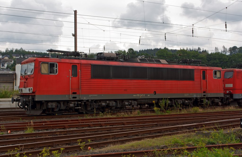 155 147-2 der DB Schenker Rail Deutschland AG abgestellt in Kreuztal am 16.08.2011. 
Diese Loks der ehem. DR BR 250 wurde in den 70er-Jahre, auf Grund der gestiegenen Leistungsanforderungen der Zugf�rderung im G�terverkehr produziert, da die E11 und E41 den Anforderungen nicht mehr gerecht wurden. 
Die Lokomotiven werden heute im gesamten Schienennetz der DB eingesetzt und sind praktisch vor jeder Art von G�terz�gen anzutreffen.
In den letzten Jahren gab es wiederholt Probleme mit den 3-achigen Drehgestellen der Loks, so dass die H�chstgeschwindigkeit zeitweise auf 80 km/h heruntergesetzt werden musste. Au�erdem wurden bereits zahlreiche Maschinen wegen diverser Sch�den und zur Gewinnung von Ersatzteilen ausgemustert. Hin und wieder wurde auch eine komplette Ausmusterung der Baureihe 155, die inzwischen zu den �lteren Triebfahrzeugen der Deutschen Bahn geh�rt, in Erw�gung gezogen. Seit Sommer 2006 werden jedoch auf Grund von Kapazit�tsmangel wieder Loks der BR 155 im AW Dessau einer Hauptuntersuchung unterzogen. 
Von einer Abstellung der gesamten Baureihe wird derzeit abgesehen.