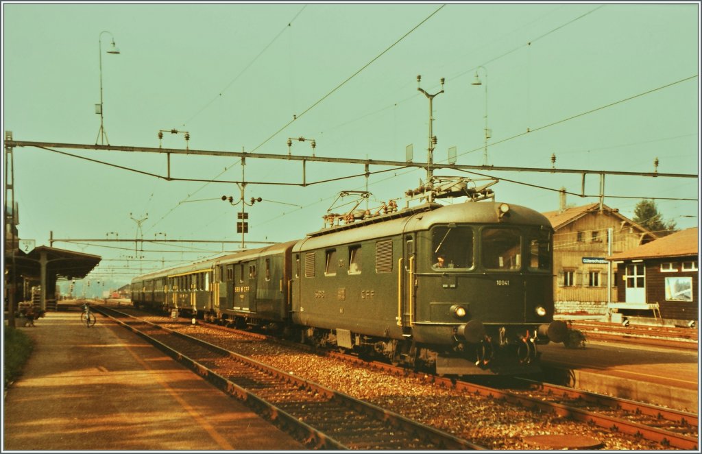 Die Re 4/4 I 10041 mit einem Schnellzug von Biel/Bienne nach Del�mont wartet in Grenchen Nord auf die Abfahrt. 
August 1984