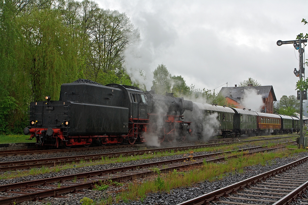 
Volldampf im Hellertal, aus Anlass: 150 Jahre Eisenbahn an Sieg, Heller, Dill und Lahn, am 06.Mai 2012: Mit 2 Stunden Versp�tung, dadurch nun im vollen Regen (Das EBA hatte bei der �berpr�fung Lok etwas beanstandet, die Kl�rung dauerte leider l�nger), kam die 23 042 vom Eisenbahnmuseum Darmstadt-Kranichstein Tender voraus aus Gie�en im Bahnhof Herdorf an.