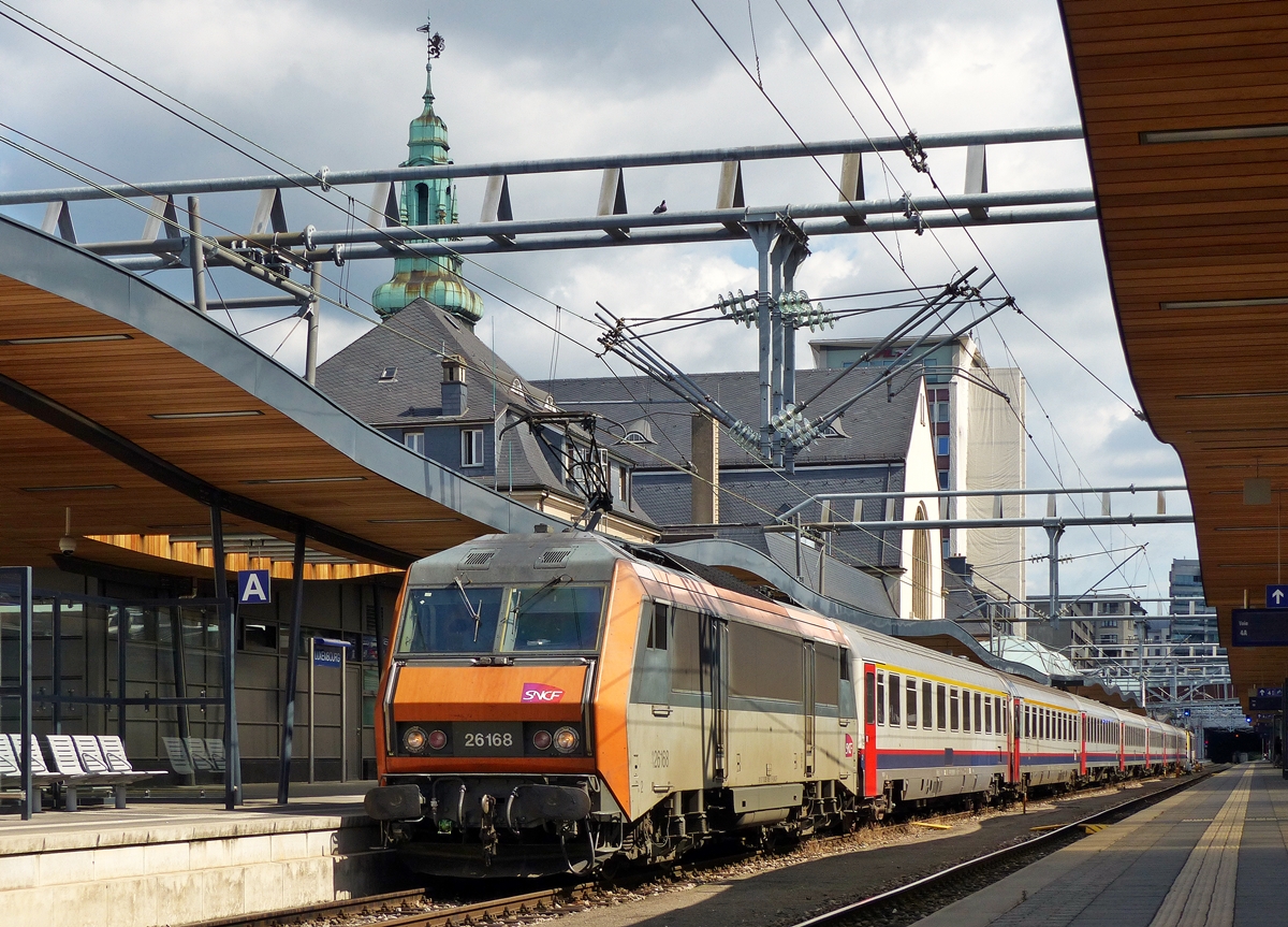 . Eigentlich wollte ich nie eine orange farbene Sybic in Luxemburg ablichten, aber die Ger�chtek�che um den ex EC Vauban brodelt wieder mal, sodass ich mich dann doch am 15.07.2014 dazu entschloss ein Bild vom ehemaligen Prestige Zug zu machen: Die SNCF BB 26168 hat den EXP 91  Vauban  Bruxelles Midi - Basel von der SNCB HLE 1349 �bernommen und steht nun abfahrbereit im Bahnhof von Luxemburg Stadt.

Nach letzen Meldungen, soll 2016 dieser Zug, sowie der EXP  Iris  definitiv abgeschafft werden. Sie sollen durch TGV nach Strasbourg ersetzt werden. Dann wird es keine direkten Verbindungen mehr zwischen Luxemburg (resp. Br�ssel) und der Schweiz geben.