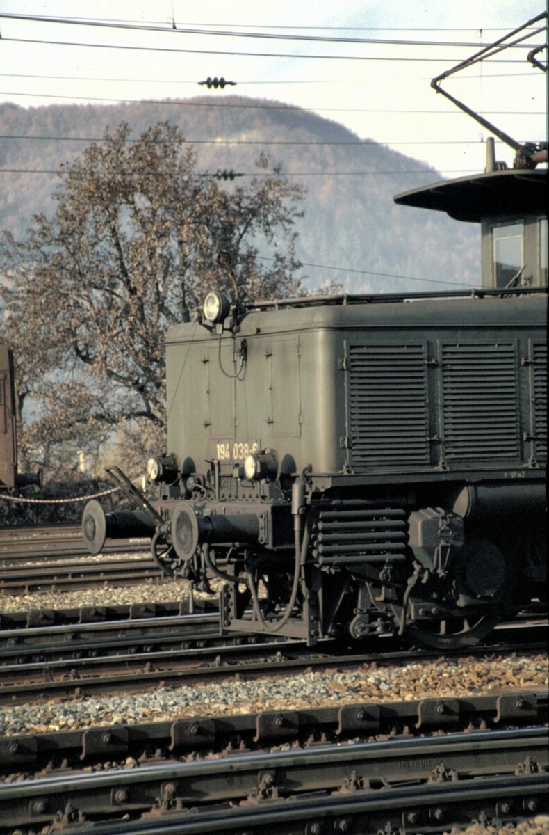 194 038-6 Schublok auf der Geislinger Steige, noch mit Kupplungsüberwurfbügel und Seilzug in den Führerstand ausgerüstet, am 11.10.1980.
Der Kupplungsüberwurfbügel war Ende 1980 bereits nicht mehr im Einsatz, da sich herausstellte, das der Bügel sich sehr leicht verhakt hat und nicht über Seilzug gelöst werden konnte. Um die Schublok vom Zug zu Lösen war ein Halt im nächsten Bahnhof mit Ausweichstelle. Das waren Westerstetten oder Ulm. So kam es vor,dass die Schublok bis Ulm mitgeschleppt wurde.
Die Einrichtung wurde bald wieder abgebaut. Somit haben diese Fotos einen gewissen Seltenheitswert.