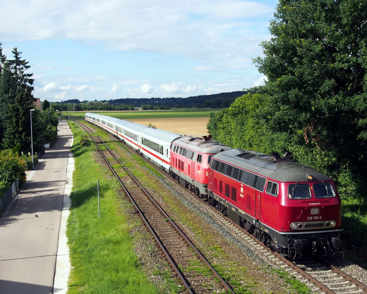 218 155-0 und 218 mit IC Allg�u fahren durch V�hringen am 02.08.2021. Mit einiger Versp�tung kam der IC Allg�u. Aufgrund eines vorausfahrenden 633, konnte der besonders lange Block V�hringen - Illertissen nicht befahren werden und der Zug h�tte im Bahnhof V�hringen halten m�ssen. Hinter der kleinen Kurve (am Ende des Zugs) wurde der Zug deutlich abgebremst und er rollte zu meiner Freude langsam an mir vorbei in den Bahnhof. Kurz vor dem Stand wurde die Strecke freigegeben und der Zug konnte wieder beschleunigt werden.