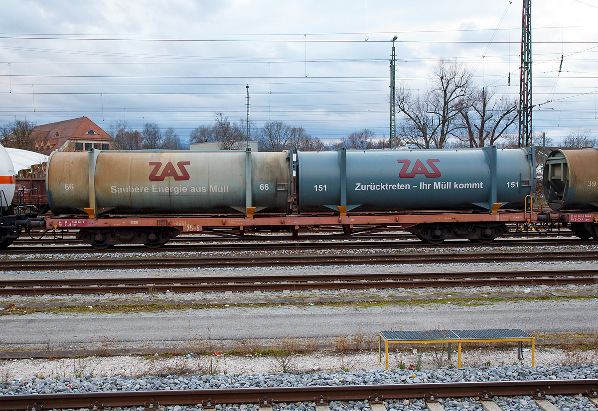 4-achsiger Drehgestell-Containertragwagen der Gattung Sgs 33 RIV 80 4540 075-5 D-ZAS der ZAS Zweckverband Abfallverwertung S�dostbayern, beladen mit zwei M�ll-Containern, abgestellt am 27.12.2016 im Bahnhof Rosenheim. 

TECHNISCHE DATEN des Wagons: 
Spurweite: 1.435 mm
Anzahl der Achsen: 4 in zwei Drehgestellen
L�nge �ber Puffer: 18.900 mm
Drehzapfenabstand: 13.000 mm
Achsabstand im Drehgestell: 2.000mm
Ladel�nge: 18.500 mm
H�chstgeschwindigkeit: 120 km/h 
Maximales Ladegewicht: 58,5 t (Streckenklasse C oder h�her)
Eigengewicht: 21.280 kg
Kleinster bef. Gleisbogenradius: 35 m
Bauart der Bremse: KE-GP

In jedem der umliegenden sechs Landkreise des Verbandsgebietes der ZAS (etwa 7350 km� - etwa 10% der Fl�che Bayerns) unterh�lt der ZAS eine M�llumladestation. Dort werden die Abf�lle gesammelt und in spezielle Gro�container (wie hier auf den Wagon zu sehen) verpresst. Der M�ll wird dabei auf ein Viertel des urspr�nglichen Volumens verdichtet. Die so bef�llten Container werden dann auf solchen Sgs Bahnwaggons gesetzt und jeden Werktag von den M�llumladestationen per Bahn zum M�llheizkraftwerk nach Burgkirchen transportiert.

Im M�llheizkraftwerk werden die Container von den Bahnwaggons �ber einen Spreader-Kran an den M�llbunker angedockt und ausgepresst. Mit diesem Logistiksystem werden ca. 70% der an das M�llheizkraftwerk angelieferten Abf�lle aus dem Verbandsgebiet umweltfreundlich per Bahn transportiert.