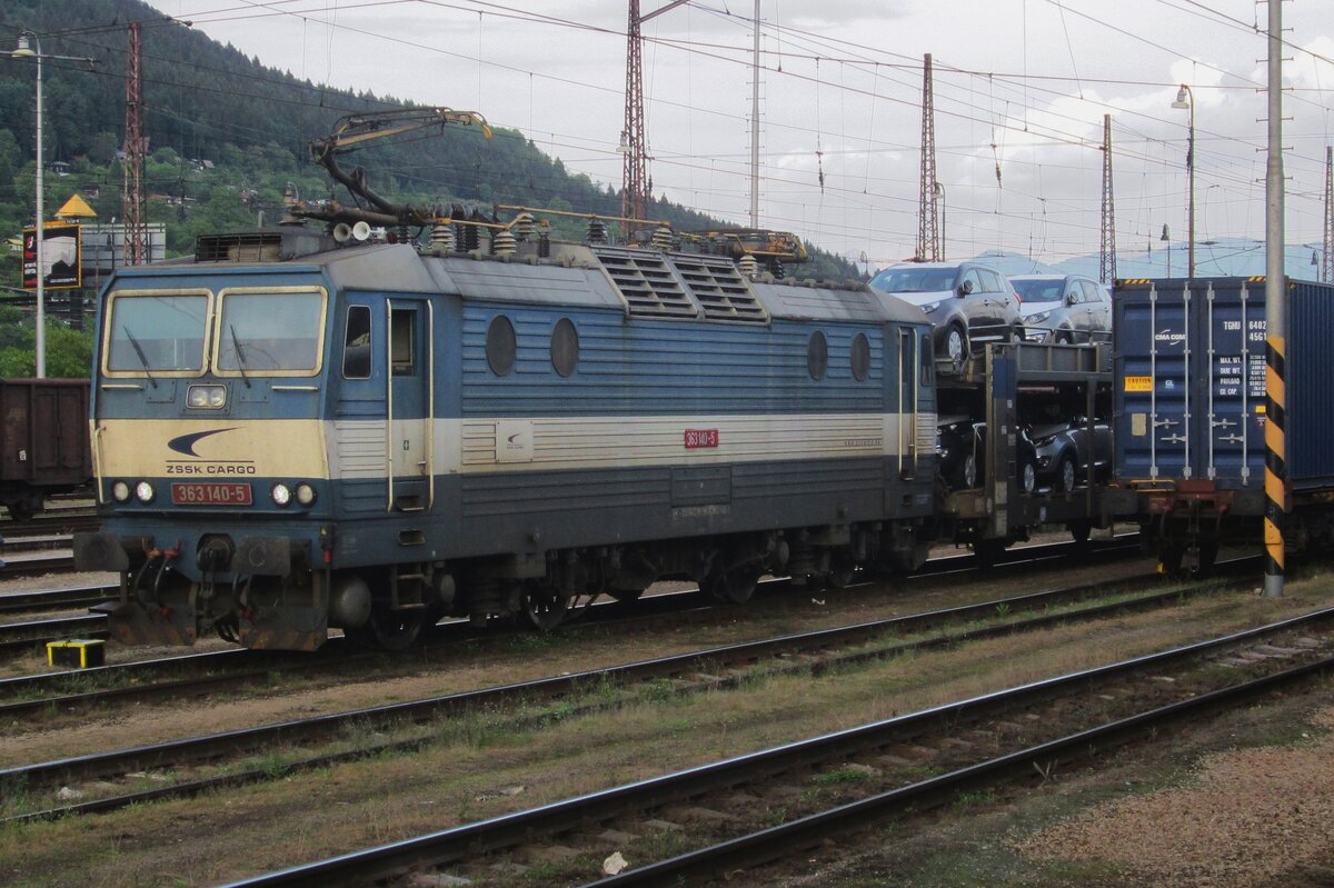 Am Abend von 29 Mai 2015 setzt sich ZSSK 363 140 vor ein KIA PKW-Zug in Zilina. Die Gegend im Hintergrund hat sich ganz erwechelt: die Guterzuggleise sind verschwunden und ein Autobahn  ziert  den Hintergrund dieses Bahnhofs.