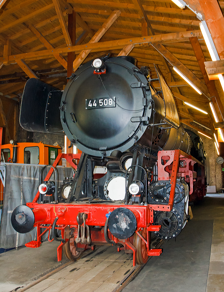 An dem Jumbo gibt es noch sehr viel Arbeit....

Die schwere Güterzug-Dampflokomotive 44 508, ex DB 044 508-0, am 18.05.2014 ausgestellt im Lokschuppen vom Erlebnisbahnhof Westerwald der Westerwälder Eisenbahnfreunde 44 508 e. V. hier war Museumstag. Die Lok ist Eigentum vom DB-Museum und eine Leihgabe an die Eisenbahnfreunde, die nach ihr ihren Verein genannt haben.

Die Dampflokomotive 44 508 wurde im Jahr 1941 von der Lokomotivfabrik Krauss-Maffei in München unter der Fabriknummer 16113 gebaut und an die DR geliefert. Nach dem Krieg blieb sie im Westen und wurde so 1949 als 44 508 in den Bestand der Deutsche Bundesbahn aufgenommen, mit der Einführung des EDV-Nummernschemas wurde sie zum 01.01.1968 in 044 508-0 umgezeichnet.
Bis zu ihrer Außerdienststellung im Jahre 1977 legte sie eine Strecke von über 1.9 Millionen Kilometern zurück.

Die Maschine verfügt über ein Drei-Zylinder-Triebwerk, fünf Antriebsachsen und einen Schlepptender, in dem sie 10 Tonnen Kohle und 34 Kubikmeter Wasser mitführen kann. Sie erreicht eine maximale Leistung von 1910 PS bei einem Dienstgewicht von 160 Tonnen. 

Die 44 508 wurde im Mai 1977 beim Bahnbetriebswerk Gelsenkirchen-Bismarck außer Dienst gestellt. Die 44 508 ist eine der letzten erhaltenen Dampflokomotiven ihrer Bauart. Sie wurde im Jahr 1987 durch eine Freizeitgruppe des Bahn-Sozialwerkes (BSW) übernommen. Damit begann die museale Aufarbeitung der Lok, die im Jahre 2002 jedoch unterbrochen wurde, als das Domizil in Siershahn geräumt werden musste. Der Verein Westerwälder Eisenbahnfreunde übernahm diese Dampflokomotive als Leihgabe des DB Museums, auch wenn sie nie im Westerwald eingesetzt war. 

Um das hohe ehrenamtliche Engagement und die damit verbundene immense Zahl von bereits geleisteten Arbeitsstunden zu würdigen, soll sie im Erlebnisbahnhof Westerwald weiterhin äußerlich aufgearbeitet werden und einen Ehrenplatz im Museum erhalten.


Die Lokomotiven der Baureihe 44 der Deutschen Reichsbahn waren schwere, fünffach gekuppelte Güterzug-Einheitsdampflokomotiven der Gattung G 56.20 mit Drillingstriebwerk. Sie waren vorgesehen für die Beförderung von Güterzügen bis 1.200 t auf Mittelgebirgsstrecken und 600 t über Steilrampen.

Im Jahr 1926 wurden 10 Prototypen gebaut, denen 1932 zwei weitere folgten. Die Serienfertigung der Baureihe 44 begann erst 1937, nachdem ihr Weiterbau anstelle der Zwei-Zylinder­Lokomotiven der Baureihe 43, die parallel zur 44 entwickelt und gebaut worden war, beschlossen wurde. Die Baureihe 44 wurde dagegen als Drei-Zylinder-Lokomotiven ausgebildet, wobei der dritte Zylinder im Rahmen unter der Rauchkammer angeordnet ist. Die großen Leistungsreserven und ihre ausgezeichnete Laufruhe wogen den Nachteil der schwierigen Unterhaltung des im Rahmen schlecht zugänglichen dritten Triebwerkes mehr als auf. So verwundert es nicht, dass die letzte Dampflokomotive, die bei der Deutschen Bundesbahn in Betrieb war, der Baureihe 44 angehörte. Es handelt sich um 44 903 Öl, die am 26.10.1977 in Emden außer Dienst gestellt wurde.


Technische Daten:
Gebaute Stückzahl: 1989
Bauart  1'E h3
Gattung:  G 56.20
Spurweite:  1435 mm (Normalspur)
Länge über Puffer:  22.620 mm
Höhe:  4.550 mm
Fester Radstand:  3.400 mm
Gesamtradstand:  9.650 mm
Dienstgewicht:  169,8 t (mit Tender)
Radsatzfahrmasse:  19,8 t
Höchstgeschwindigkeit: 80 km/h (rückwärts nur 50 km/h)
Leistung:  1.910 PS (1.405 kW) bei Lok mit Ölfeuerung 2.100 PS
Treibraddurchmesser:  1.400 mm
Laufraddurchmesser vorn:  8.50 mm
Zylinderanzahl:  3
Zylinderdurchmesser:  550 mm
Kolbenhub:  660 mm
Kesselüberdruck:  16 bar
Rostfläche:  4,55 m²
Überhitzerfläche:  100,00 m²
Verdampfungsheizfläche:  237,67 m²
Bremse:  selbsttätig wirkende Einkammerdruckluftbremse Bauart Knorr
Steuerung:  Bauart Heusinger

Tender: 2´2´T34
Kohlenvorrat:  10 t
Wasservorrat: 34 m3
