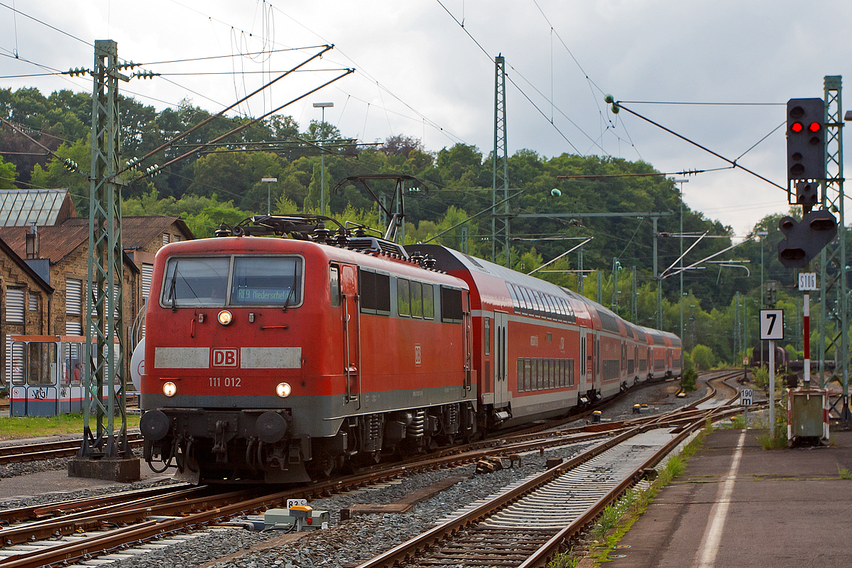 
Bis Mitte August 2014 ist für den RE 9 (rsx - Rhein-Sieg-Express) in Niederschelden Endstation, der Grund dafür ist der Weiterbau der Hüttentalstraße (HTS) als B 62. Diese Hochstraße überquert in Niederschelden die Siegstrecke (KBS 460). 
Hier fährt die 111 012-1 der DB Regio NRW mit sechs Doppelstockwagen als RE 9  rsx - Rhein-Sieg-Express  (Aachen- Köln - Niederschelden) am 13.07.2014 in den Bahnhof Betzdorf/Sieg ein. 

Ungewöhnlich ist das eine 111er mit sechs DoSto´s fährt. 

Die Lok wurde 1975 von Krauss-Maffei in München unter der Fabriknummer 19749 gebaut, der elektrische Teil ist von Siemens. Sie hat seit 2007 die NVR-Nummer 91 80 6111 012-1 D-DB und die EBA-Nummer EBA 01C20A 012.
