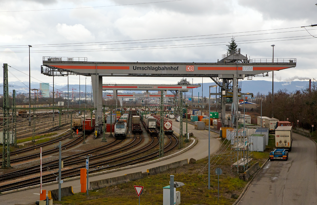
Das Tor zur Schweiz, nach Italien und Frankreich. Blick von der Friedensbr�cke auf den DB Umschlagbahnhof Basel - Weil am Rhein  der DUSS (Deutsche Umschlaggesellschaft Schiene-Stra�e) am 28.12.2017. 

Direkt im Grenzgebiet zwischen Deutschland, der Schweiz und Frankreich liegt das Terminal Basel–Weil am Rhein auf der EU-Au�engrenze im Dreil�ndereck. Das Terminal liegt auf der Nord-S�d-Schienenachse Frankfurt–Karlsruhe–Basel mit Anschluss an die norditalienischen Industriezentren. Besonders wegen seiner geografischen Lage gilt das DUSS-Terminal als wichtige logistische Drehscheibe f�r alpenquerende KV-Transporte in und aus der Schweiz, f�r den Transit nach Italien sowie ins benachbarte Frankreich. Die Anlage bietet au�erdem gute Umsteigem�glichkeiten f�r Feeder-Verkehre und beg�nstigt somit die Bildung effizienter Transportnetzwerke der Kunden.

Das Terminal ist gut erreichbar �ber die Autobahn A5/E 35 Karlsruhe–Basel, Ausfahrt Weil am Rhein, oder die A36/E60 aus Frankreich kommend in die A5 m�ndend. Der Rangierbahnhof Weil am Rhein ist dem Terminal n�rdlich vorgelagert und bietet Anschluss an das deutsche und schweizerische Schienennetz.