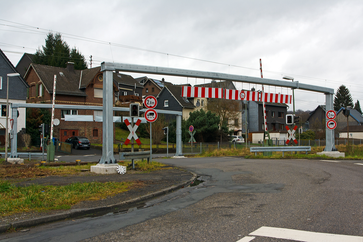 
Der Bahnübergang  in Mudersbach an der Siegstecke, KBS 460  (Bü km 114,7) am 21.12.2014. 

Seit Mai 2014 gibt es die Hindernisse für größere LKW vor jeder Seite, da Verbotsschilder nicht ausreichten (bzw. manche die Abmessungen ihres Fahrzeuges nicht kennen. 

Wie man sieht geht es stumpf um die Ecke (die gegenüber liegende Straße geht parallel zur Bahnstrecke weiter) und da hat sich schon mancher LKW verkeilt d.h. kam nur durch mehrmaliges Rangieren weiter. So kam es hier schon mehrfach zu Unfällen mit dem Zugverkehr, die Schranke schloss aber es hing noch ein LKW fest. Am 26. November 2013 hatte sich z.B. ein Sattelzug sich am Bahnübergang festgefahren und der Regionalexpress RE 9 war in ihn gefahren, zum Glück ohne größere Katastrophe. Drei Personen wurden dabei leicht verletzt, neben dem Zugführer und einem Fahrgast auch ein Passant, der sich in der Nähe aufhielt.
