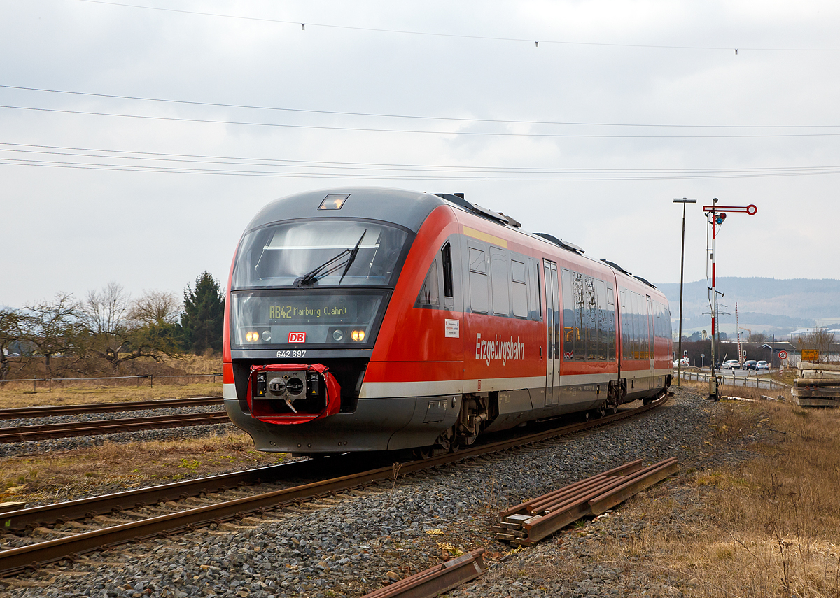 
Der Desiro 642 697 / 642 197 (95 80 0642 697-6 D-DB / 95 80 0642 197-7 D-DB)  Thermalbad Wiesenbad  der Kurhessenbahn fährt am 24.03.2018, als RB 42 von Brilon Stadt via Willingen nach Marburg/Lahn, durch (Lahntal-) Sarnau. 

Der Dieseltriebzug wurde 2003 von Siemens in Uerdingen unter den Fabriknummern 92939 und 92938 gebaut. Bis Dezember 2017 war er bei der Erzgebirgsbahn (DB Regio) im Einsatz, nun fährt er für die Kurhessenbahn (DB Regio).


Ende der 1990er Jahre schrieb die DB eine größere Anzahl von Dieseltriebwagen aus, mit dem Ziel, den Betrieb auf Nebenbahnen wirtschaftlicher zu gestalten und dort die verbliebenen lokbespannten Züge abzulösen. Es wurden gut 500 Triebwagen, aufgeteilt in acht Baureihen, bei der Fahrzeugindustrie bestellt. Die stückzahlenmäßig größte Baureihe war der Desiro von Düwag bzw. Siemens, er wurde als Baureihe 642 in 231 Exemplaren beschafft.


Technik und Aufbau:
Der Wagenkasten ist aus selbsttragenden Aluminiumröhre in Integralbauweise konstruiert. Die Kopfteile mit den Führerständen sind als vorgefertigte GfK-Module ausgeführt, die auf das verlängerte Untergestell des Aluminiumwagenkastens aufgeklebt sind.

Der Fahrgastraum ist gegliedert in den Niederflurbereich (von einem Einstieg bis zum Sitzbereich über dem Jakobsdrehgestell) und die höher gelegenen Bereiche an jedem Wagenende. Aufgrund des vergleichsweise großen Motorraums besitzt die Baureihe 642 jedoch einen geringeren Niederfluranteil als vergleichbare Züge wie zum Beispiel Bombardier Talent oder Alstom Lint. Glaswände und -türen trennen Einstiegsräume und Übergangsbereiche voneinander ab.

Der Fahrgastraum wird durch eine Warmwasser-Umluft-Heizung, bei extremer Kälte durch Ölfeuerung geheizt. Im Sommer soll die Klimaanlage für behagliche Temperaturen sorgen, allerdings sind die Anlagen noch immer störanfällig. Pro Wagen können sechs Fenster gekippt werden.


Fahrwerke und Bremsen
Zwei angetriebene Drehgestelle, ein nicht angetriebenes Jakobsdrehgestell mit Gummiprimärfedern und niveauregulierter Luftfederung in der Sekundärstufe. Je drei Wellenbremsscheiben
je Triebdrehgestell, zwei Radbremsscheiben je Radsatz im Jakobsdrehgestell. Magnetschienenbremse in den Triebdrehgestellen. Mikroprozessorgesteuerter Gleit- und Schleuderschutz. Die Triebwagen sind mit einer direkten elektropneumatischen Bremse (ep-Bremse) und einer indirekten mehrlösigen Druckluftbremse als Rückfallebene ausgestattet. Mit dem Retarder wird bei Nutzung der ep-Bremse zudem hydrodynamisch gebremst. Als Feststellbremse sind Federspeicherbremsen vorhanden. Die Magnetschienenbremse kommt bei Zwangs- und Schnellbremsungen zum Einsatz, bei Notbremsungen jedoch bleibt sie unwirksam. Zudem kann sie vom Triebfahrzeugführer über einen Kippschalter zugeschaltet werden.

Antrieb
Der Triebzug wir von zwei MTU 6-Zylinder-Dieselmotor mit Abgasturboaufladung, Ladeluftkühlung mit jeweils 275 kW / 374 PS Leistung (Euro II) bei 1900 U/min angetrieben. (Bei anderen Kunden und Ausführungen auch 315, 335 oder 360 kW, sowie Motoren von MAN)
Diese befinden sich jeweils unter dem Hochflurbereich zwischen dem angetriebenen Drehgestell und dem Niederflurbereich. Ihr Drehmoment wird über ein hydromechanisches Fünfgang-Automatikgetriebe mit Anfahrwandler und integriertem Retarder auf das äußere Drehgestell übertragen.

Technische Daten (DB Regio Version) : 
Spurweite:  1.435 mm (Normalspur)
Achsformel:  B´2´B´
Länge über Kupplung:  41.700 mm
Drehzapfenabstand: 2 x 16.000 mm
Achsabstand im Drehgestell: 1.900 / 2.650 /1.900 mm
Lauf- und Treibraddurchmesser: 770 mm (neu) / 710 mm (abgenutzt)
Breite:  2.830 mm
Größte Höhe: 3.819 mm
Fußbodenhöhen: 1.250 mm (Hochflur) / 575 mm (Niederflurbereich)
Eigengewichtgewicht: 68,2 t
Zul. Gesamtgewicht:  88,7 t
Höchstgeschwindigkeit:  120 km/h
Motoren: zwei MTU 6-Zylinder-Dieselmotor 
Leistung: 2 x 275 kW / 374 PS
Kraftübertragung: mechanisch (5-Gang-Automatikgetriebe mit hydraulischen Anfahrwandler)
Kraftstoffvorrat:  2 x 600 l
Heizölvorrat:  2 x 150 l
Max. Anfahrbeschleunigung: 1,1 m/s²
Max. Bremsverzögerung: Betriebsbremse 0,9 m/s² / Gefahrbremse 1,15 m/s²
Sitzplätze: 12 (1.Klasse) 109 (2.Klasse, davon 13 Klappsitze)
Stehplätze:  90
Scharfenberg Kupplung:  Typ 10
