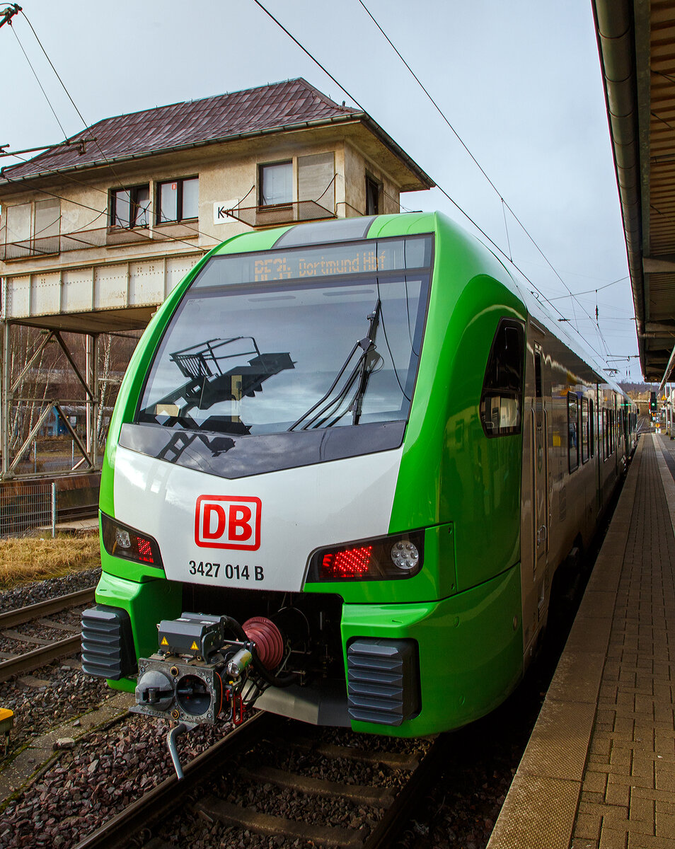 Der für die DB Regio AG – NRW fahrende dreiteilige Stadler FLIRT 3 XL 3427 014 (94 80 3427 014-0 D-STAP / 94 80 3827 014-6 D-STAP / 94 80 3427 514-9 D-STAP) der ZV VRR Eigenbetrieb Fahrzeuge und Infrastruktur, am 15.12.2022, als RE 34 „Dortmund-Siegerland-Express“ (Siegen - Letmathe - Dortmund), beim Halt im Bahnhof Kreuztal. Links das ehem. Reiterstellwerk Kreuztal Nord (Kn).

Der Stadler FLIRT 3 XL wurde 2020 von der Stadler Pankow GmbH in Berlin unter den Fabriknummern 42354 bis 42356 gebaut und an den Zweckverband Verkehrsverbund Rhein-Ruhr Eigenbetrieb Fahrzeuge und Infrastruktur geliefert. Eigentlich war dieser FLIRT 3 XL wie 9 weitere für die Bedienung der Regiobahnstrecke S 28 Kaarst - Neuss - Düsseldorf - Mettmann - Wuppertal vorgesehen, wo die Elektrifizierung bis 2020 erfolgen sollte. Da aufgrund von Verzögerungen der elektrische Betrieb voraussichtlich erst 2026 aufgenommen werden kann, wurden die inzwischen gelieferten Triebwagen u. a. von der DB Regio AG NRW eingesetzt.

Stadler FLIRT 3 XL, dreiteilig der BR 3427:
Die Fahrzeuge der BR 3427 vom Typ STADLER Flirt 3 XL sind, in der sogenannten XL-Ausführung, mit 67.600 mm um 4,4m länger als die normalen STADLER Flirt 3 (BR 1427), zudem haben diese 6 Türen pro Fahrzeugseite (anstatt 3). Der FLIRT verfügt über eine hohe Antriebsleistung (2.720 kW) und eine maximale Geschwindigkeit von 160 km/h. Die 3-Teiler haben 180 Sitzplätze (16 in der 1.Klasse und 154 in der 2. Klasse).

Der VRR Auftrag umfasste die Lieferung von 41 Triebzügen des Typs FLIRT. Die Bestellung teilte sich auf in 17 dreiteilige und 24 fünfteilige Fahrzeuge. Beide Fahrzeugvarianten verfügen über längere Wagenkästen, der sogenannten XL-Ausführung (FLIRT 3 XL). Ergänzend wird Stadler auch die Instandhaltung der Fahrzeuge in den kommenden 30 Jahren verantworten. Die Fahrzeuge kommen auf den Strecken des S-Bahn-Netzes Rhein-Ruhr zum Einsatz. Der FLIRT verfügt über eine hohe Antriebsleistung und eine maximale Geschwindigkeit von 160 km/h. Der helle, freundliche Fahrgastbereich ist barrierefrei und bietet dem Betreiber individuelle Gestaltungsmöglichkeiten. Sie verfügen über bequemere Sitze, überwiegend in 4er-Sitzgruppen mit Vis-à-vis-Anordnung, Toiletten sowie Steckdosen zum Aufladen von Smartphones, Tablets oder Rechnern.

Technik:
• Ausgelegt für die Verbandsfahrt von bis zu 3 Fahrzeugen
• Automatische Mittelpufferkupplungen (Scharfenbergkupplung)
• Leichtbauweise aus Aluminium
• Redundante Antriebsausrüstung bestehend aus 2 Antriebssträngen mit je einem Transformator, IGBT-Stromrichter und 2 Asynchronfahrmotoren
• Luftgefederte Fahrwerke sorgen für die erforderliche Laufruhe
• Die Fahrzeuge wurden in zwei unterschiedlichen Designs ausgeliefert (S-Bahn Rhein-Ruhr Design [grün/weß] sowie Regiobahn Design [rot/weiß])

Komfort:
• Klare Trennung von Mehrzweckbereichen für den Fahrradtransport sowie für die Beförderung von Rollstuhlfahrern
• 12 Fahrradstellplätze
• 2 extrabreite zweiflügelige Schwenkschiebetüren je Wagenkasten
• Klimatisierter Fahrgastraum und Fahrerraum
• 1 geschlossenes WC-System je EMU3 bzw. 2 geschlossene WC-Systeme je EMU5
• Einstiegshöhe 780 mm
• Modernes Fahrgastinformationssystem
• Passagier-WLAN im ganzen Fahrgastraum

TECHNISCHE DATEN (BR 3427 - Stadler FLIRT 3 XL, dreiteilig):
Spurweite: 1.435 mm (Normalspur)
Achsanordnung: Bo' 2' 2' Bo'
Länge über Kupplung: 67.600 mm
Fahrzeugbreite: 2.820 mm
Fahrzeughöhe: 4.270 mm
Fußbodenhöhe Niederflur: 780 mm
Fußbodenhöhe Hochflur: 1.150 mm
Einstiegsbreite: 1.800 mm je Tür 
Anzahl der Türen je Fahrzeugseite: 6
Sitzplätze: 180 (1. Klasse 16 / 2. Klasse 164)
Stehplätze (4 Pers./m²): 260
Dienstgewicht: 
Achsabstand im Drehgestell: 2.700 mm
Lauf- und Triebraddurchmesser: 870 mm (neu)
Höchstgeschwindigkeit: 160 km/h
Max. Leistung am Rad: 2.720 kW
Dauerleistung am Rad: 2.000 kW
Max. Anfahrbeschleunigun: 1,2 m/s²
Kupplung: Scharfenbergkupplung (Schaku) Typ 10

Quellen: Stadler Rail