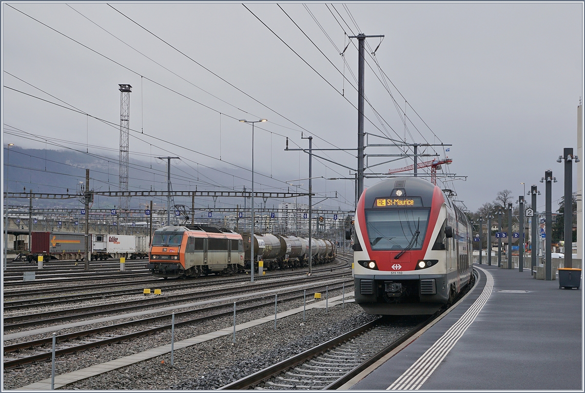 Der SBB RABe 511 110 nach St-Maurice erreicht Lancy Pont Rouge, während im Güter- bzw. Rangierbahnhof Genève La Praille gleich gegenüber die SNCF BB 26211 wartet.

13. Februar 2020