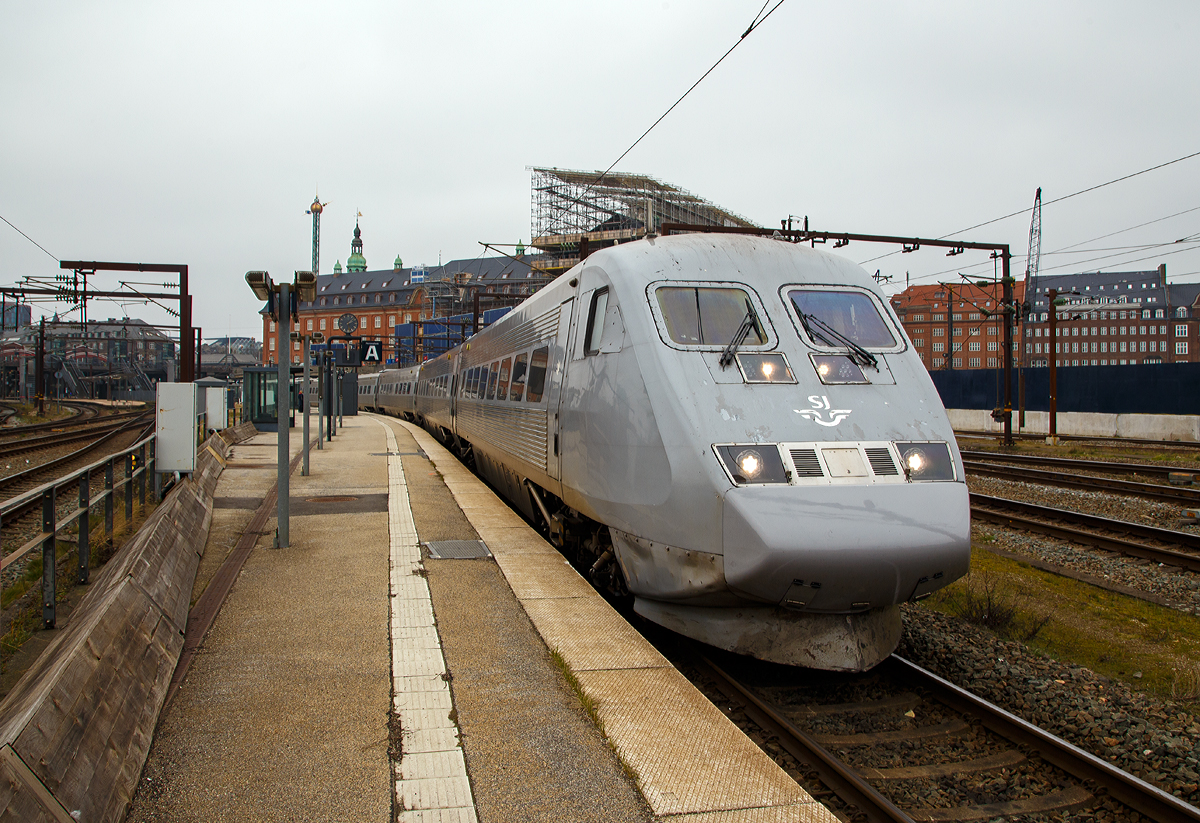
Der sechsteilige X2K 2033 (S-SJ 93 74 302 2033-8) der SJ (Statens Järnvägar AB, ehemaligen schwedische Staatsbahnen, steht am 20.03.2019 auf Gleis 26 im Hauptbahnhof Kopenhagen (dän. Københavns Hovedbanegård), als X2 542 nach Stockholm Central zur Abfahrt bereit.

Die Baureihe SJ X2 sind Hochgeschwindigkeitszüge der schwedischen Staatsbahngesellschaft SJ AB. Sie sind allgemein unter dem Markennamen X2000 bekannt. Verbindungen mit diesen Zügen werden in Schweden an den Bahnhofs-Anzeigen als Snabbtåg (deutsch Schnellzug) geführt. Ein Zug besteht aus einem Triebkopf, vier bis fünf Mittelwagen und einem Steuerwagen. In einem der Mittelwagen befindet sich ein Zugrestaurant. Die Vielfachsteuerung ermöglicht, zwei Einheiten zu kuppeln. Damit entsteht ein Zug mit elf Wagen und zwei Triebköpfen. 

Durch die im Vergleich zu Mitteleuropa gänzlich andere Bevölkerungsstruktur in Schweden bot es sich nicht an, teure Hochgeschwindigkeitsstrecken zu bauen. Die hügelige und bergige Landschaft Schwedens verteuerte Neubaustrecken noch zusätzlich.

Daher entschieden sich die Schwedischen Staatsbahnen (SJ) für einen Triebzug der Baureihe X2 mit Neigetechnik, mit dem bestehende Strecken schneller befahren werden können. Die Bezeichnung X2000 wurde als Produktname des Hochgeschwindigkeitsverkehrs gewählt. Wobei an den Bahnhofs-Anzeigen sucht man vergeblich an dieser Bezeichnung, sondern sie werden als Snabbtåg (deutsch Schnellzug) angezeigt.

Die Züge sind vollklimatisiert. Die vorgesehene fahrplanmäßige Höchstgeschwindigkeit lag bei 200 km/h, die Züge waren technisch für 210 km/h ausgelegt. Zehn der zwanzig Einheiten waren für die Strecke Stockholm–Göteborg bestimmt, weitere Garnituren sollten auf den Strecken Stockholm–Malmö und Stockholm–Östergötland eingesetzt werden. Die Züge wurden im Werk Västerås der ABB zu einem Stückpreis von 100 Millionen Schwedischen Kronen gebaut; die Entwicklung der Züge hatte bis 1989 zwei Milliarden Kronen gekostet.

Jeder Triebkopf besitzt vier Drehstrom-Asynchronmotoren. Die Steuerung erfolgt mittels GTO-Thyristoren mit einer Frequenz zwischen 0 und 120 Hz. Die maximale Achslast liegt bei 18,5 Tonnen.

Die Neigetechnik wird richtungsabhängig von einem Beschleunigungsmesser im führenden Fahrzeug gesteuert. Der Neigungswinkel ist abhängig von Geschwindigkeit und Bogenradius, er wird in jedem Wagen an den Drehgestellen gemessen und hydraulisch eingestellt. Die Neigung liegt bei maximal 6,5 Grad, die Neigungsänderung bei höchstens vier Grad pro Sekunde. Bei Geschwindigkeiten unter 70km/h ist die Neigetechnik nicht aktiv. Die Technik wird so eingeschränkt, dass ein Reisender auf einem Eckplatz des Wagens nie 30 cm höher oder tiefer als ein anderer im selben Wagen sitzt. Die Triebköpfe selbst verfügen über keine Neigetechnik. Ein besonderer Lokführersitz mit verstärktem Seitenhalt gleicht die erhöhte Seitenbeschleunigung aus.

Eine Besonderheit der Züge ist die radiale Einstellbarkeit der einzelnen Achsen in jedem Drehgestell. Auf den bogenreichen Strecken Schwedens kann sich so jede Achse einzeln der Strecke anpassen. Dadurch reduziert sich die Reibung erheblich, was zu Einsparungen beim Energieverbrauch und geringerem Materialverschleiß führt.

In den Jahren 2000 bis 2001 wurden die Züge X2 2031–2034 und 2036–2043 für den Betrieb in Dänemark umgerüstet, damit der Einsatz auf der Öresundverbindung möglich wurde. Neben dem Einbau der dänischen Zugbeeinflussungseinrichtung beinhaltete dies die Umrüstung der Triebköpfe für den Zweifrequenzbetrieb, da die dänischen Fernstrecken abweichend mit 25kV bei 50Hz elektrifiziert sind. Die Baureihenbezeichnung dieser Triebköpfe änderte sich auf X2K.

Der Zug hat spürbare Auswirkungen auf die SJ und den schwedischen Schienenverkehr hinterlassen. Steigende Passagierzahlen, verbunden mit sinkenden Betriebsausgaben bei gleichzeitig beschleunigten und effizienteren Einsätzen halfen den SJ, profitabel zu werden.

TECHNISCHE DATEN:
Hersteller: ABB (Västerås), Kalmar Verkstad (Kalmar)
Baujahre: 1989 bis 1998
Gebaute Garnituren: 43
Spurweite: 	1435 mm (Normalspur)
Achsformel: Bo'Bo' (Triebkopf)
Länge über Kupplung: 140m (fünfteilig) / 165m (sechsteilig)
Leergewicht: 344 t (fünfteilig) / 391 t (sechsteilig)
Höchstgeschwindigkeit: 200 km/h
Dauerleistung: 3.260kW
Stromsystem: 15 kV 16,7 Hz AC (Baureihe X2K zusätzlich 25kV/50Hz AC für den Verkehr nach Dänemark)
Sitzplätze: 	263 (fünfteilig) / 311 (sechsteilig)
