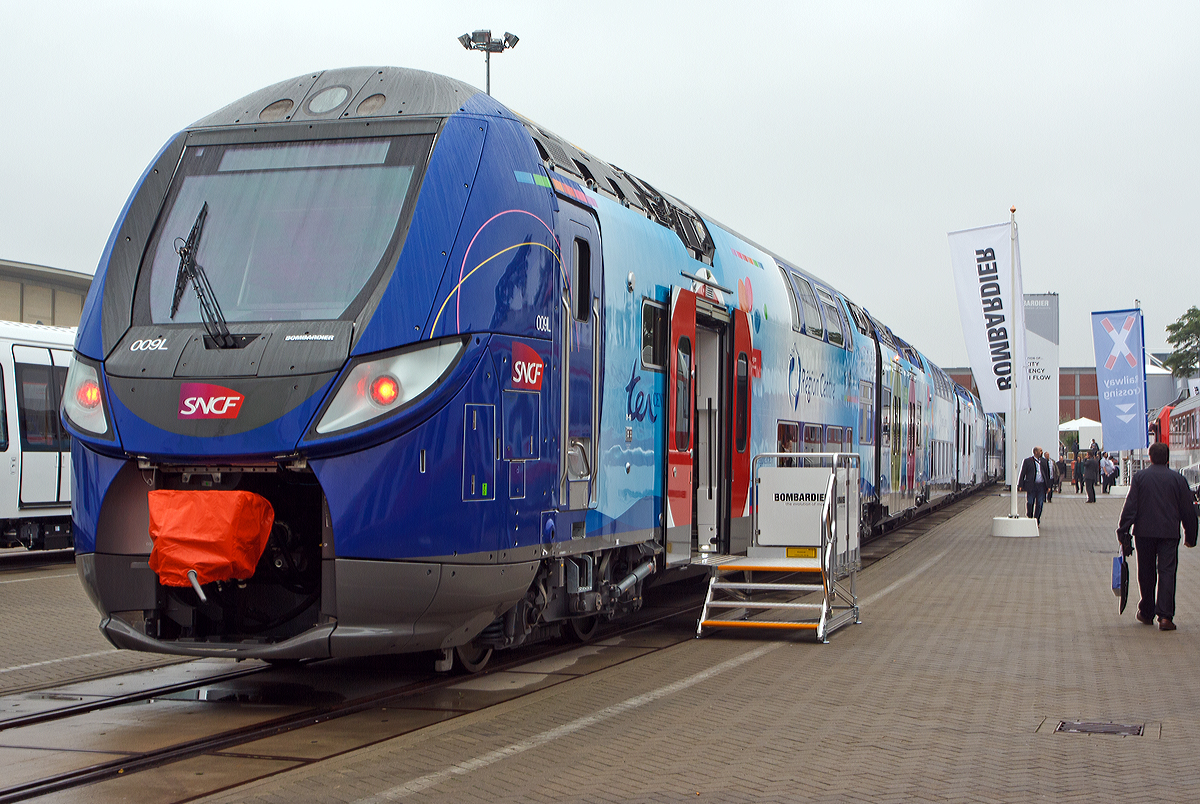 
Der SNCF R�gio2N Triebzug (Rames) 009L (Baureihe Z 55500), hier Z 55517/18 der ter R�gion Centre ein achtteiliger elektrischer Doppelstocktriebzug vom Typ Bombardier OMNEO wurde auf der Inno Trans 2014 in Berlin pr�sentiert, hier am 26.09.2014. Die Endwagen haben die NVR-Nummern 94 87 55 00 517-0 F-SNCF und 94 87 55 00 518-1 F-SNCF.

Die SNCF hat bis Ende 2013, f�r zehn Regionen,  207 Z�ge (6, 7, 8 oder 10-teilig) fest bestellt, zudem gibt es eine Option �ber 653 weitere Z�ge. Diese R�gio2N-Z�ge sind Gliedertriebz�ge mit Jakobs-Drehgestellen. Der Zug besteht abwechselnd aus einst�ckigen und doppelst�ckigen Wagen, welche im Baukastenprinzip miteinander kombiniert werden k�nnen. Die Z�ge bestehen aus bis zu vier verschiedenen Wagentypen: einst�ckige Endwagen (14,30 m), doppelst�ckige Endwagen (19,21 m), ein- (10,02 m) und doppelst�ckige Mittelwagen. Die doppelst�ckigen Mittelwagen k�nnen in kurzer (13,69 m) und langer (15,44 m) Ausf�hrung gebaut werden. Die doppelst�ckigen Mittelwagen weisen keine T�ren auf, letztere befinden sich in den einst�ckigen Mittelwagen (2 T�ren pro Fahrzeugseite) und den Endwagen (jeweils eine pro Fahrzeugseite). Die T�ren sind 1,6 m breit und die Einstiegsh�he betr�gt 60 cm �ber Schienenoberkante. Auf den einst�ckigen Mittelwagen befinden sich zudem die Stromabnehmer.

Es werden verschiedene Zugkonfigurationen angeboten. Die hier pr�sentierte Garnitur ist wie folgt zusammengestellt:
einst�ckiger Endwagen, 14.300 mm lang, mit einer T�r/Seite;
doppelst�ckiger Mittelwagen,15.445 mm lang;
einst�ckiger Mittelwagen,10.200 mm lang, mit zwei T�ren/Seite;
doppelst�ckiger Mittelwagen,15.445 mm lang;
einst�ckiger Mittelwagen,10.200 mm lang, mit zwei T�ren/Seite;
doppelst�ckiger Mittelwagen,15.445 mm lang;
einst�ckiger Mittelwagen,10.200 mm lang, mit zwei T�ren/Seite, sowie 
doppelst�ckiger Endwagen, 19.210 mm lang, mit einer T�r/Seite.

Die Innenausstattung l�sst sich entsprechend den Anforderungen des Bestellers anpassen. Dazu k�nnen die Sitzaufteilung (2+1-, 2+2- oder 2+3-Bestuhlung) und der Sitzabstand (gr��ere Beinfreiheit auf �berregionalen Strecken) ver�ndert werden.

Au�ergew�hnliche Kapazit�t und erh�hter Fahrgastkomfort (laut Hersteller):
-	Ein innovatives Zugkonzept mit ein- und zweist�ckigen Waggons
-	Drei Meter breite Wagenk�sten
-	15% mehr Kapazit�t im Vergleich zur 2+2 Sitzkonfiguration (verglichen mit der 2+2 Variante bei traditionellen Doppelstockz�gen)
-	Stufenloser Einstieg an allen Fahrgastt�ren
-	MITRAC  TM1510 PS Permanentmagnetmotor f�r weniger angetriebene Achsen durch h�here Leistungsdichte


Technische Daten Z55 500 (8-teilig) der ter R�gion Centre
Hersteller: Bombardier
Spurweite: 1435 mm (Normalspur)
L�nge �ber Kupplung: 109.910 mm
Breite des Fahrzeuges einst�ckiger Wagen: 3.050 mm
Breite des Fahrzeuges zweist�ckiger Wagen:2.997 mm
H�he des Fahrzeuges: 4.320 mm
Sitzpl�tze: 515
H�chstgeschwindigkeit: 160 km/h (Z56500 - V200 intercity 200km/h)
Dauerleistung:  2.550 kW
Antrieb: 4 Synchronmotoren mit Dauermagneten
Stromsystem:  1,5 kV DC / 25 kV 50 Hz AC
