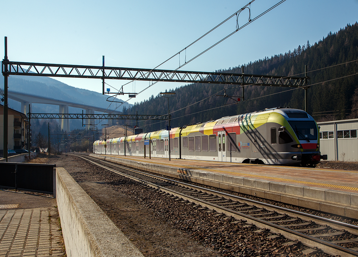 Der Trenitalia ETR 170 217, ein sechsteiliger Stadler FLIRT (MS für I / A) erreicht am 27.03.2022, als Regionalzug von Meran/Merano via Bozen/Bolzano nach Brenner/Brennero, den Bahnhof Gossensaß/Colle Isarco. 

Diese sechsteiligen Elektrotriebzüge vom Typ Stadler FLIRT wurden für den grenzüberschreitenden Verkehr zwischen Italien und Österreich konzipiert. Die 160 km/h schnellen Züge werden auf den Linien Meran-Bozen-Brenner, Unterland Trento-Ala und Franzensfeste-Innichen-Lienz (Pustertal) eingesetzt. Die aktuelle Flotte besteht derzeit aus 25 FLIRTs. Sie sollen auch noch im Vinschgau (Meran-Mals), unter 25 kV 50 Hz, eingesetzt werden. Sie sind mit dem Zugsicherungssystem ETCS ausgestattet. Der klimatisierte Innenraum und das offene und transparente Design machen die Reise mit angenehm für die Passagiere. Ein modernes Informationssystem versorgt die Fahrgäste mit allen notwendigen Informationen, sie sind zudem mit WLAN ausgestattet.

Im Hintergrund das Wipptal überbrückende Gossensaß-Viadukt (Viadotto Colle Isarco) der Brennerautobahn.