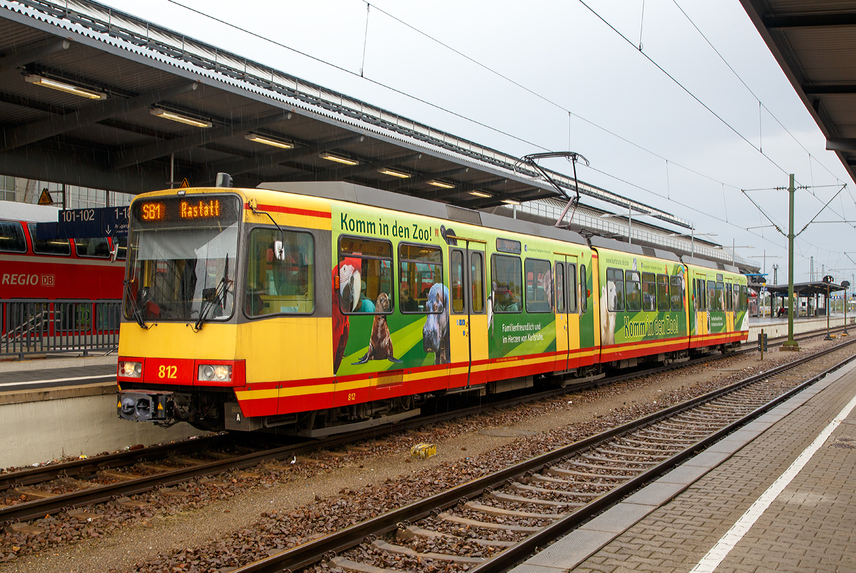 Der Zweisystem-Stadtbahn-Triebzug 812 der VBK Verkehrsbetriebe Karlsruhe GmbH (VBK 812) steht am 09.09.2017, als Linie S 81nach Rastatt, zur Abfahrt im Hbf Karlsruhe bereit.

1991 wurde nach mehrj�hriger Entwicklungsarbeit die erste Serie Zweisystem-Stadtbahnfahrzeug ausgeliefert. Mit diesen Fahrzeugen begann eine neue �ra im Schienenverkehr. Denn diese Fahrzeuge sind in der Lage, sowohl im Netz der DB, im Eisenbahnnetz der AVG als auch im Stra�enbahnnetz der VBK zu fahren.

Um dieses zu k�nnen, sind sie in zahlreichen Bereichen mit zwei Systemen, dem der DB wie dem von AVG und VBK ausgestattet, z. B verf�gen sie �ber zwei unterschiedliche Funksysteme und �ber zwei unterschiedliche Sicherungssysteme. Der Clou der Fahrzeuge aber ist die automatische Umschaltung von einer Strom- und Betriebsart auf die andere. Der Triebfahrzeugf�hrer muss nichts machen, das Fahrzeug schaltet an den Systemwechselstellen selbstst�ndig von 750 V auf 15 KV oder umgekehrt um.

Bei den Fahrzeugen handelt es sich um achtachsige, dreiteilige Gelenktriebwagen mit zwei Jakobsdrehgestellen. Die beiden �u�eren konventionellen Drehgestelle am Bug und Heck werden von zwei Gleichstrommotoren mit 280 kW angetrieben. Der mechanische Aufbau der Fahrzeuge ist von den seit 1983 in Karlsruhe eingesetzten Stadtbahnen GT6-80C und GT8-80C abgeleitet, welche selbst vom DUEWAG Stadtbahnwagen Typ B abgeleitet wurden. 

Im Gegensatz zu diesen Stadtbahnen handelt es sich allerdings um Zweirichtungswagen, da im DB-Netz im Allgemeinen keine Wendeschleifen existieren. Daher verf�gen sie �ber zwei Fahrerkabinen und jeweils vier Doppelt�ren auf jeder Fahrzeugseite. Die Wagenk�sten sind in Ganzstahlbauweise ausgef�hrt. Scharfenberg-Kupplungen erlauben einen Betrieb in Mehrfachtraktion, darunter Doppel- und Dreifachtraktionen sowie gemischte Doppeltraktionen mit den GT6-80C, GT8-80C und GT8-100D/2S-M.

Die elektrische Ausr�stung der GT8-100C/2S wurde von den GT8-80C �bernommen und besteht aus je einem Gleichstrom-Fahrmotor pro Antriebsdrehgestell sowie einer Gleichstromstellersteuerung.
Als Zweisystemwagen verf�gen die Stadtbahnen �ber die notwendigen technischen Einrichtungen, um sowohl unter der Stra�enbahnoberleitung mit 750 V Gleichspannung als auch unter der Eisenbahnfahrleitung mit 15 kV 16,7 Hz Wechselspannung verkehren zu k�nnen. Diese Einrichtungen sind auf dem Wagendach sowie unter dem Fu�boden des Fahrzeug-Mittelteils untergebracht und bestehen aus einem f�r beide Systeme geeigneten Einholm-Stromabnehmer, einem Stromsystem-Pr�fsystem, einem pneumatischen System-Wahlschalter, einem Transformator sowie einem Gleichrichter mit Gl�ttungsdrossel.Der �bergang zwischen beiden Stromsystemen erfolgt automatisch. Eine R�ckspeisung durch die Rekuperationsbremse ist nur bei 750 Volt Gleichspannung m�glich.

Im Rahmen der Kooperation zwischen AVG/VBK und der DB beschaffte auch die DB Regio AG vier Fahrzeuge.

Insgesamt wurden 36 Wagen gebaut, von denen 35 noch fahren, einer wurde bei einem Brand vollkommen zerst�rt.
AVG-Fahrzeuge: 813 - 815 und 826 - 836
VBK-Fahrzeuge: 801 - 812 und 821 - 825
DB-Fahrzeuge: 816 – 820

Die Fahrzeuge sind jeweils als Stra�enbahnen gem�� der BOStrab und als Eisenbahnfahrzeuge gem�� der EBO zugelassen. Zwei unterschiedliche Funksysteme und zwei unterschiedliche Sicherungssysteme (Stra�enbahn/Eisenbahn)

TECHNISCHE DATEN:
Bauart: achtachsiger Zweisystemstadtbahnwagen in Zweirichtungsbauweise
Baujahr: 1991-1994
Hersteller Untergestell/Drehgestell: ABB Henschel Waggon Union GmbH, Werk Siegen
Hersteller Wagenkasten: Siemens-Duewag-Schienenfahrzeuge GmbH, Werk D�sseldorf
Hersteller Elektrik: ABB Daimler-Benz Transportation (ADtranz) / Siemens
Spurweite: 1.435 mm (Normalspur)
Achsanordnung: 	B'2'2'B'
Anzahl der Achsen: 8 (davon 4 angetriebene Achsen)
L�nge �ber Kupplung: 37.610 mm
L�nge �ber Wagenkasten: 36.570 mm
Drehzapfenabstand: 10.100 mm / 9.770 mm /10.100 mm
Achsabstand im Drehgestell: 2.100 mm
Treibraddurchmesser: 	770 mm
Breite: 2.650 mm
H�he: 3.700 mm
Fu�bodenh�he:  1.000 mm
Sitz-/Stehpl�tze: 100 / 115
Zahl der T�ren: 2 x 4 Doppelt�ren
Leergewicht: 58,6 t
Dienstgewicht: 73,5 t (2/3 besetzt)
H�chstgeschwindigkeit: 90 km/h 
Gesamtleistung: 2 x 280 kW
Beschleunigung: 0,85 m/s�
Bremsverz�gerung: 1,6 m/s�
Stromversorgung: 750 V Gleichstrom oder 15 KV 16,7 Hz Wechselstrom
Das Fahrzeug schaltet an den Systemwechselstellen selbstst�ndig von 750 V auf 15 KV oder umgekehrt um.
