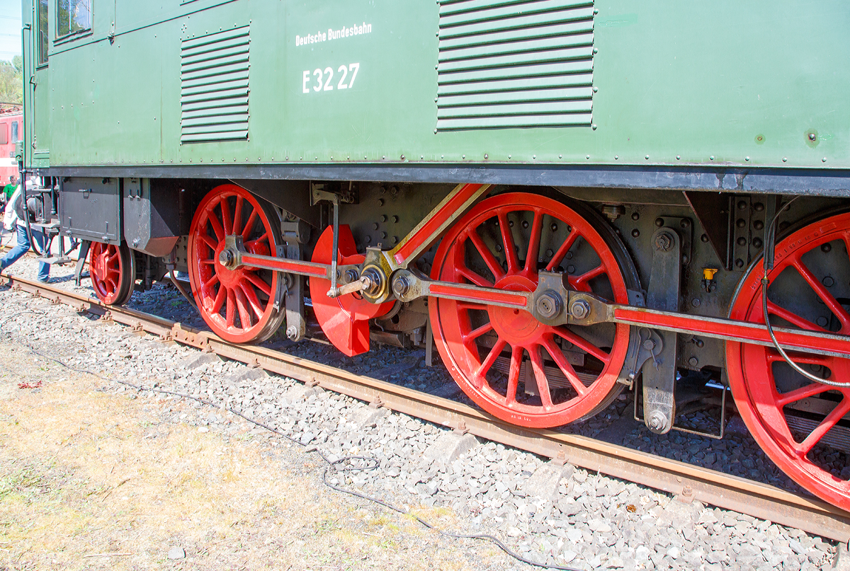 
Detailbild vom Triebwerk und Schr�gstangenantrieb der  E 32 27, ex 132 027-4, ex Bay. EP 2 20 027 am 30.04.2017 im Eisenbahnmuseum Bochum-Dahlhausen.

Die E 32 besa� langsam laufende hochliegende Repulsionsmotoren. Diese nahmen wegen ihrer Gr��e den ganzen Querschnitt des Lokomotivkastens ein, fr�her hatten solche Motoren eine beachtliche Gr��e. F�r die �bertragung der Antriebskraft von diesem wurde in einem Winkel von ungef�hr 45� angeordnete Treibstange angebracht. Die Treibstange �bertrug die Kraft auf die Blindwelle, von der die Kraft mittels Kuppelstangen auf drei Achsen �bertragen wurde. Zwischen dem Rechten und Linken Triebwerk war ein Kurbelversatz von 90�. Damit ist immer eine Antriebsseite in der Lage, die Antriebskr�fte aufnehmen und �bertragen zu k�nnen, wenn die andere Seite im Totpunkt ist.
