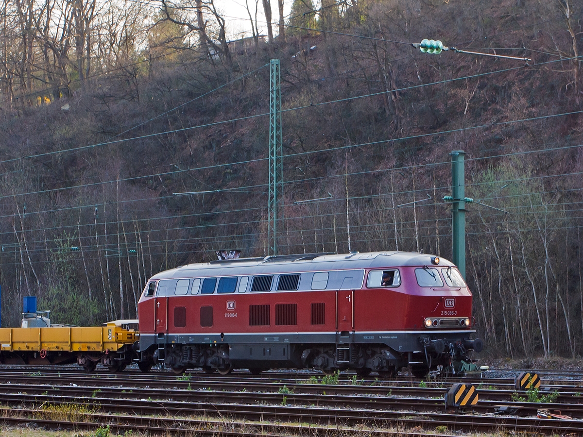Die 215 086-0 (eigentlich 225 086-8) der RE - Rheinische Eisenbahn am 27.03.2014 rangiert einen Bauzug in Betzdorf/Sieg.

Die V 163 wurde 1971 bei MaK unter der Fabriknummer 2000091 und an die DB ausgeliefert, 2001 ging sie an die DB Cargo AG und wurde in 225 086-8 umbezeichnet, ob sie die Dampfheizung behaten hat kann ich nicht genau sagen. Mit der Ausmusterung bei der nunmehrigen DB Schenker Rail Deutschland AG im Jahr 2011 erfolgte auch der Verkauf an die RE - Rheinische Eisenbahn, hier wurde sie wieder in den Auslieferzustand zur�ckversetzt und tr�gt nun wieder die Bezeichnung 215 086-0 ist aber weiter einer 225er (NVR-Nummer 92 80 1225 086-8 D-EVG).

Die Lokomotiven der Baureihe 215 wurden kurzfristig als Variante der V160-Familie f�r den Personen- und G�terverkehr beschafft und dabei im Gegensatz zu anderen Baumustern der V160-Familie mit Heizdampferzeugern ausger�stet. Geplant war sie im alten Baureihenschema als V 163. Diese Lokomotiven sollten sp�ter in die Baureihe 218 umgebaut werden k�nnen. Dazu erhielt sie bereits den um 400 Millimeter verl�ngerten Lokkasten anderer bis dahin nur als Prototyp vorhandener Baureihen. Der Hauptgrund f�r den Bau der Baureihe 215 lag darin, dass die Reihe 218 noch nicht Serienreife erreicht hatte, die Bundesbahn aber die restlichen noch vorhandenen Dampflokomotiven ersetzen wollte. 1968 bis 1970 wurden insgesamt 150 Lokomotiven gebaut.

Mitte der 1980er erhielten die Maschinen mit 12-Zylinder-V-Motor Abgashutzen auf dem Dach (wie diese). Sie bewirkten eine Beschleunigung und Umlenkung der Abgase, so dass bei klimatisierten Reisezugwagen, welche auf dem Dach die Luftansaug�ffnungen hatten, eine Bel�stigung der Fahrg�ste durch Abgase oder Abgasger�che vermieden wurde. Weiterhin sorgten die Hutzen noch f�r andere Effekte: die bis zu 280 �C hei�en Abgase wurden V-f�rmig an der Oberleitung vorbeigeleitet, so dass die Oberleitung nicht verru�t wurde und sich nicht zu sehr ausdehnte. Au�erdem wurde die Gefahr von B�schungsbr�nden durch herabsinkende, hei�e Ru�partikel reduziert. Auch eine T�rschlie�anlage und Bremsgest�ngesteller zum automatischen Nachstellen des Bremskolbenhubes wurden nachger�stet.

Technische Daten:
Achsformel:  B'B'
Spurweite:  1.435 mm
L�nge:  16.400 mm
Drehzapfenabstand:  8.600 mm
Drehgestellachsstand:  2.800 m
Gesamtradstand: 11.400 mm
Gewicht: 79 Tonnen
Radsatzfahrmasse:  20,0 Tonnen
H�chstgeschwindigkeit: 140 km/h (90 km/h im Rangiergang) Motorentyp: MTU MA 12 V 956 TB 10 (ein V12-Zylinder-Diesel-Motor), 
Dauerleistung: 1.840 kW (2.500 PS)
Nenndrehzahl: 1500 min-1
Leistungs�bertragung: hydraulisch, �ber Kardanwellen vom mittig angeordneten Getriebe zu den beiden zweiachsigen Drehgestellen. So werden �ber Radsatzgetriebe jeweils beide und somit alle Achsen angetrieben. Ein Wendegetriebe erm�glicht den Richtungswechsel.
Getriebe: Voith L 820 brs  
Tankinhalte: 3.050 l (Kraftstoff) / 2.850 l (Wasser) / 690 l (Heiz�l) / 320 kg Sand
Zugheizung:  Dampf