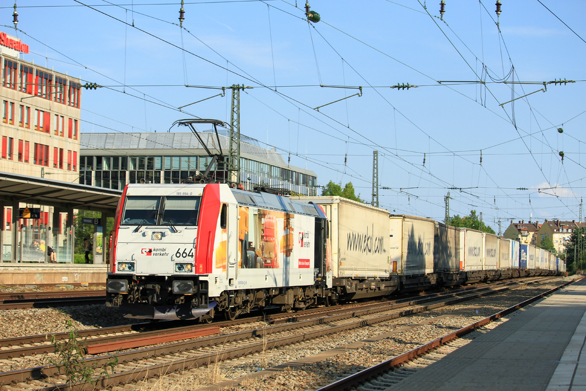Die f�r Kombiverkehr werbende 185 664 () durchf�hrt mit einem Klv den Bahnhof M�nchen Heimeranplatz in Richtung Laim. Das Foto entstand am fr�hen Abend des 17.August 2018.