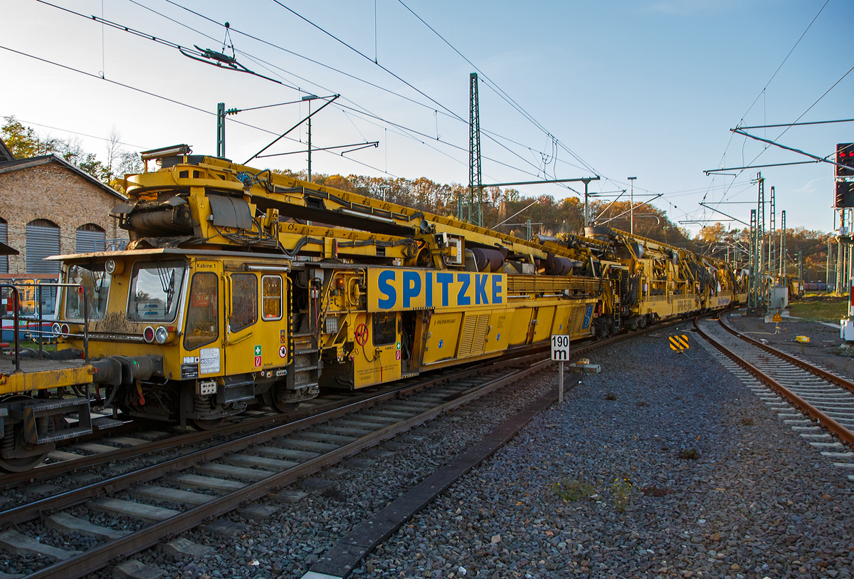 Die Plasser & Theurer Planumssanierungs- und Reinigungsmaschine RPM-RS-900 „Katharina die Große“ der SPITZKE SE (Großbeeren), Schweres Nebenfahrzeug Nr. D-SPAG 99 80 9415 004 – 1 (ex 97 19 35 501 18-1), am 09.11.2021 bei einer Zugdurchfahrt in Betzdorf (Sieg) in Richtung Siegen. Vermutlich hat der sehr lange Zug einen Abstecher nach Betzdorf gemacht, damit die Arbeitsrichtung der Maschinen richtig herum stand. 

Da die Maschine nicht auf ganze Bild passt, folgen diesem Bild noch einige Detailbilder.

Neben der über 198 m langen Maschinen bestand der Zug noch aus einigen MFS-Wagen sowie einigen Güterwagen. Der Zug wurde von der SPITZKE eigenen Siemens Smartron 192 007-3 / E 192-SP-100 gezogen.

Die Maschine wurde 2007 von Plasser & Theurer gebaut und besteht im Einzelnen aus:
• Antriebswagen ATW, 99 80 9415 004 – 1 D-SPAG (ex 97 19 35 501 18-1), Fabriknummer 4795
• Siebwagen, Fabriknummer 4796
• Schotteraufbereitungswagen, Fabriknummer 4797
• Aushubmaschine , Fabriknummer 4798
• Stopf-u.  Einschotterungsmaschine SEM, Fabriknummer 4799
• Materialförder- und Siloeinheit MFS 40 D mit Doppelförderband, 99 80 9552 098-2 D-SPAG (ex 97 19 21 558 57-5). Fabriknummer 2140, Baujahr 1992 und 2007 umgebaut
• Übergabewagen mit Kehrbürste für Schotter (RPM-RS 900 UEW), 99 80 9515 002-0 D-SPAG (ex 97 19 35 901 58-9), Fabriknummer 4800


Der große Unterschied zwischen Planumsverbesserungsmaschine und Bettungsreinigungsmaschinen besteht darin, dass Planumsverbesserungsmaschine nicht nur den Schotter ausheben und recyceln kann sondern auch einen Teil des Planums (Unterbau) ausheben. So hat sie auch zwei Aushubketten, eine für den Schotter und eine für das Planum. Zudem kann die RPM vor der Neuschotterung (Recycling- mit Neumaterial) auch wieder eine neue Planumsschutzschicht (PSS-Material) einbringen.

Die RPM-RS-900 wurde für die Planumssanierung und Schotterbearbeitung von Gleisen konzipiert und ist die längste Maschine des SPITZKE-Technikparks. Ihre Stärke liegt in ihrer Vielseitigkeit. Innerhalb eines Maschinenkomplexes werden Planumsverbesserung, Bettungsreinigung und Schotterrecycling realisiert. Der Schotter wird ausgebaut, recycelt, wieder eingebaut, verdichtet und stabilisiert. Der Boden wird ausgehoben, das neue PSS-Material eingebaut, planiert und verdichtet. Alle Arbeitsgänge verlaufen gleisgebunden, ohne Sperrung des Nachbargleises. Das ermöglicht kurze Sperrzeiten und eine hohe Verfügbarkeit des Fahrweges.

TECHNISCHE DATEN:
Spurweite: 1.435 mm
Gesamtlänge über Puffer: 198.240 mm (ohne zus. MFS Wagen)  
max. Breite / max. Höhe : 3.000 mm / 4.650 mm
Fahrzeugprofil: G 2
Gesamtgewicht (leer): ca. 800 t
Gesamtleistung:  ca. 2.800 kW
max. Geschwindigkeit geschleppt: 100 km/h
max. Geschwindigkeit Eigenantrieb: 19 km/h (bei 800 t, bis zu 15 ‰)


Quelle: SPITZKE, eisenbahndienstfahrzeuge.de

Wer noch etwas mehr über die Maschine wissen will, hier der Link zu SPITZKE: http://www.spitzke.com/maschinen/fahrweg/planumsverbesserung-bettungsreinigung-recycling/rpmrs900/