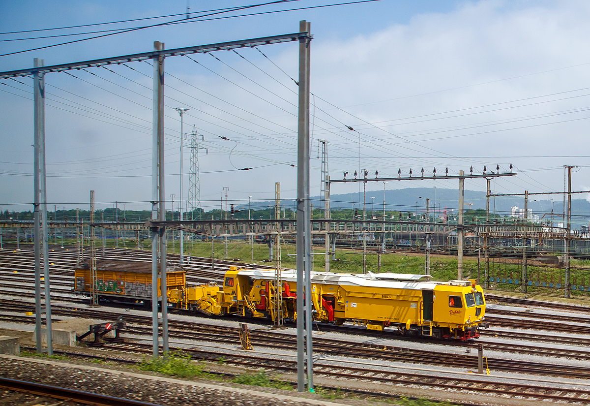 Die Stopfmaschine B66U-5  (VTmaas 80 85 95 81 905-9) der Sersa Group AG steht am 18.05.2018, mit einem angehangen gedeckten Werkstattwagen bei Basel. Aufgenommen aus einem fahrenden ICE.

Die Stopfmaschine ist eine Hochleistungs-Universal-Stopfmaschine (einschl. Schotter-Kehrb�rste am Anh�nger) vom Typ Matisa B 66 UC

Die B 66 UC ist eine Hochleistungs-Stopfmaschine, die sich durch Stopfwerkzeuge mit einer Reichweite von 2800 mm ab Gleismitte auszeichnet. Sie ist insbesondere f�r die Bearbeitung von Weichen bestimmt ist. Die vier Stopfeinheiten k�nnen unabh�ngig voneinander in  allen drei Achsen bewegt werden, was sie besonders auszeichnet. Der seitliche Verfahrweg erm�glicht das Stopfen des abgehenden Stranges bis zu einem Abstand von 2.800 mm ab Gleisachse, w�hrend die L�ngsbeweglichkeit �ber 560 mm das Unterstopfen der schr�g verlegten Langschwellen vereinfacht.

TECHNISCHE DATEN:
Spurweite: 1.435 mm 
Achsfolge: Bo´2´(ohne Anh�nger) / im Arbeitsmodus Bo´Bo´ 
Eigengewicht: 89 t
L�nge �ber Puffer : 34.485 mm    
Drehzapfenabst�nde: 15.500 mm
Achsabstand der Drehgestelle: 1.800 mm
Raddurchmesser: 840 mm
H�chstgeschwindigkeit: 100 km/h (Eigen) / 100 km/h geschleppt
Leistung des Dieselmotors:  563 kW 
Min. Kurvenradius im Fahrbetrieb: R 90 m (R 150 m im Zugverband)
Min. Kurvenradius im Arbeitsbetrieb: R 150 m
