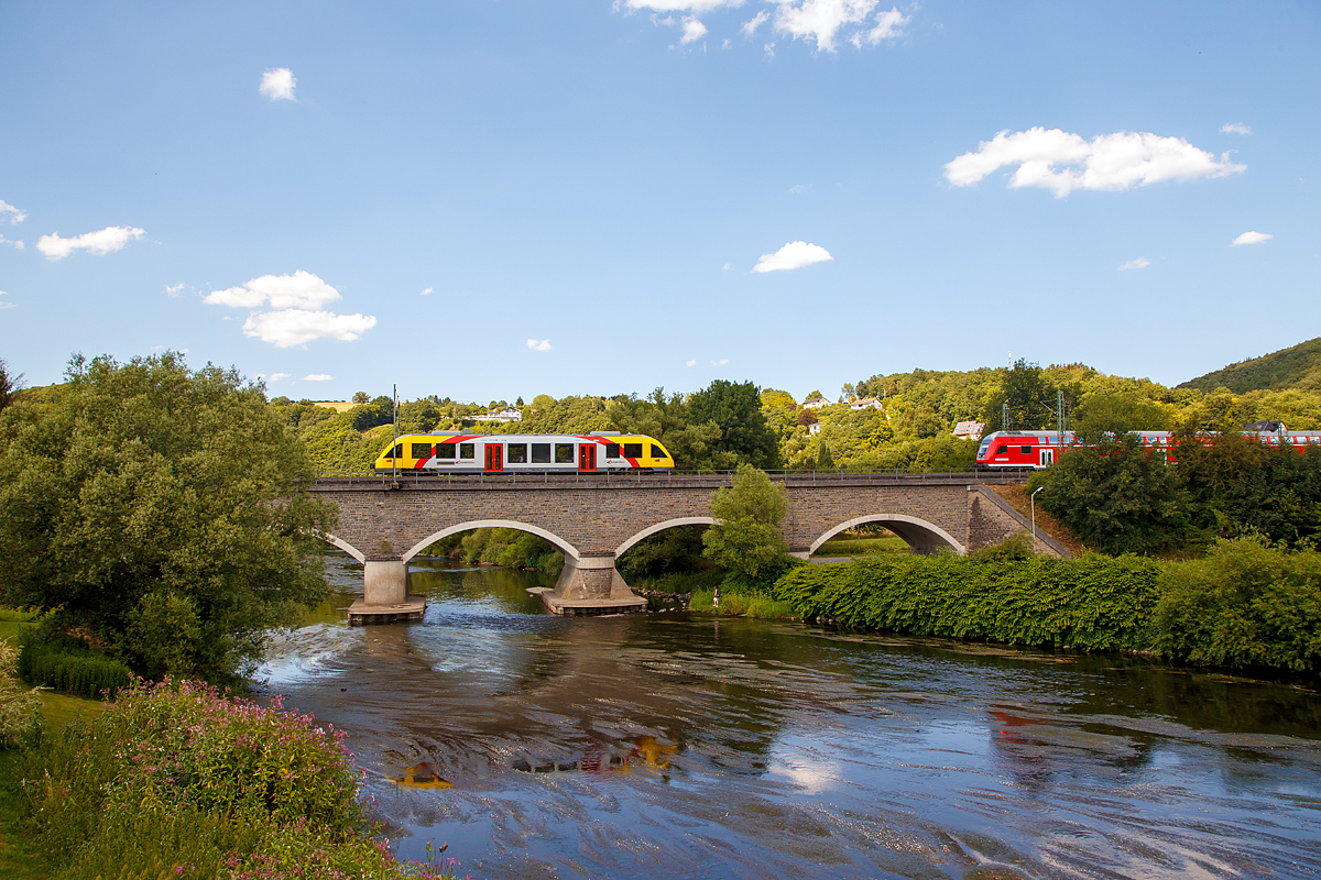 
Ein Alstom Coradia LINT 27 der HLB (Hessische Landesbahn), als RB90 Au(Sieg) - Betzdorf - Siegen, �berquert am 15.07.2018 bei F�rthen-Oppertsau die Sieg, w�hrend gerade der RE 9 bald Au (Sieg) erreicht.