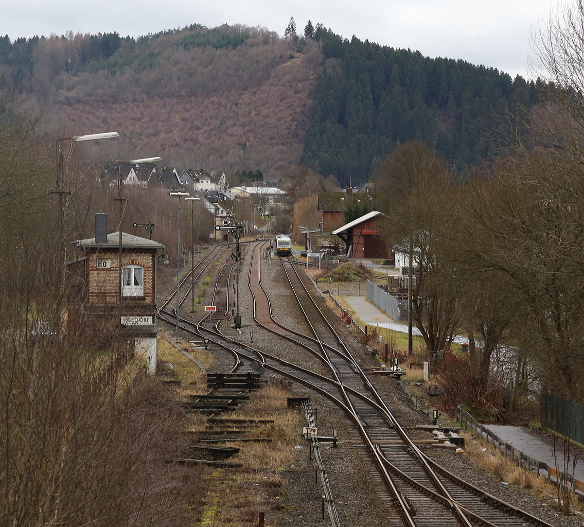 
Ein Blick am 09.01.2014 von der Brücke Wolfsweg ( Achenbachs Brücke ) auf den Bahnhof Herdorf, wo gerade der Dieseltriebwagen VT/VS 51 (BR 628.4) der Westerwaldbahn als RB 96  Hellertal Bahn  (Neunkirchen-Herdorf-Betzdorf) hält. 
Gut zu sehen sind auch die beiden Stellwerke, vorne links das Wärterstellwerk Herdorf Ost (Ho) und im Hintergrund das Fahrdienstleiterstellwerk Herdorf (Hf).
