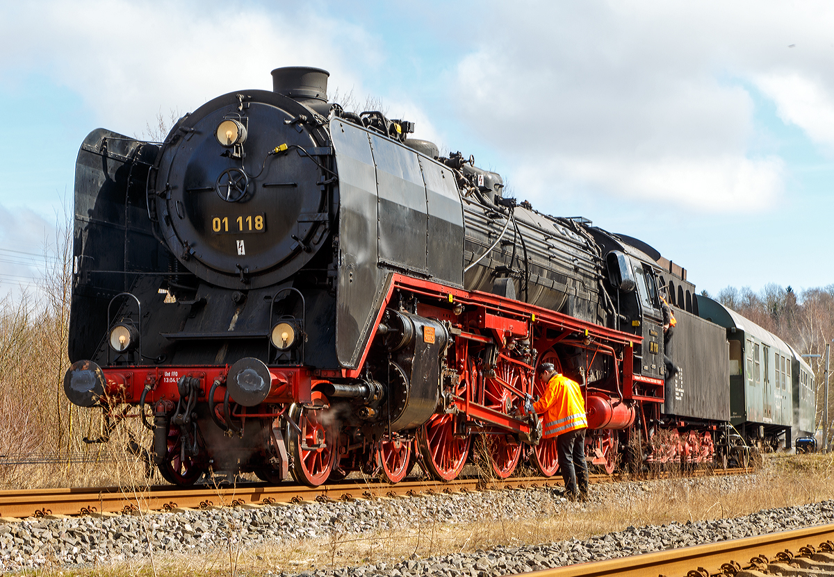 Nach der Fahrt ist vor der nächsten Fahrt, und so muss auch eine Dampflok vor der Rückfahrt wieder ordentlich geschmiert werden.

Die Zweizylinder- Schnellzuglokomotive  01 118 der HEF (Historischen Eisenbahn Frankfurt e. V.), ex DR 01 2118-6, hat am 22.03.2015 mit dem Dampfsonderzug  WESTERWALD EXPRESS  als Eilzug 25710  (Frankfurt a.M. - Limburg/Lahn - Hachenburg) den Bahnhof Hachenburg erreicht. 

Die Dampflokomotiven der Baureihe 01 waren Zweizylinder-Heißdampf-Schnellzuglokomotive für den schweren Schnellzugdienst. Sie waren die ersten in Serie gebauten Einheitsdampflokomotiven mit der Achsfolge 2’C1’ (auch Pacific genannt). Einige Lokomotiven der Baureihe 01 wurden in den 1960-er Jahren von der Deutschen Reichsbahn rekonstruiert und dann als Baureihe 01.5 eingereiht.

Zu unterscheiden von den Zweizylindermaschinen der Baureihe 01 sind die Dreizylindermaschinen der Baureihe 01.10.  Einige Zweizylindermaschinen der Baureihe 01 wurden in den 1960-er Jahren von der Deutschen Reichsbahn rekonstruiert und dann als Baureihe 01.5 eingereiht.

Die 01 118 wurde 1934 von der Lokomotivfabrik Krupp in Essen unter der Fabriknummer 1415 gebaut. Der heute mit der Lokomotive gekuppelte Tender wurde von Borsig in Berlin im Jahr 1941 mit der Fabriknummer 15117 geliefert. Der Kaufpreis für die Lokomotive mit Tender betrug damals (1934) 208.597,00 Reichsmark.

Zum Ende des zweiten Weltkrieges verblieb die Lokomotive in der damaligen Sowjetzone (späteren DDR) und wurde in den Bestand der Deutschen Reichsbahn eingegliedert. In ihren letzten Betriebsjahren bekam die Lokomotive bei der DR eine computergerechte Betriebsnummer 01 2118-6. Sie blieb von dem Umbau und Modernisierungsprogramm verschont und konnte so ihr ursprüngliches Erscheinungsbild bis zur Übernahme durch die Historische Eisenbahn Frankfurt e.V. erhalten. Bis zu ihrem Erwerb 1981 legte sie laut Betriebsbuch insgesamt stolze 3.559.271 km zurück. 

Technische Daten der Schnellzug - Dampflokomotive 01 118:
Spurweite: 1.435 mm
Bauart: 2`C1`h2
Treibraddurchmesser:  2.000 mm
Laufraddurchmesser vorn / hinten: 1.000 mm / 1.250 mm
Länge über Puffer: 23.940 mm
Zylinderdurchmesser: 600 mm
Kolbenhub: 660 mm
Kesselüberdruck: 16 bar
Höchstgeschwindigkeit vorwärts /rückwärts: 130 / 80 km/h
Leistung: 1.648 kW (ca. 2.240 PS)
Rostfläche: 4,32 m²
Verdampfungsheizfläche: 247,15 m²
Überhitzerheizfläche: 86,5 m²
Achslast max.: 20,0 t
Lokdienstgewicht: 111,3 t
Fahrzeugdienstgewicht (Lok mit Tender): 170,6 t
Wasservorrat:  34 m³ 
Kohlevorrat: 10 t

Quelle: HEF
