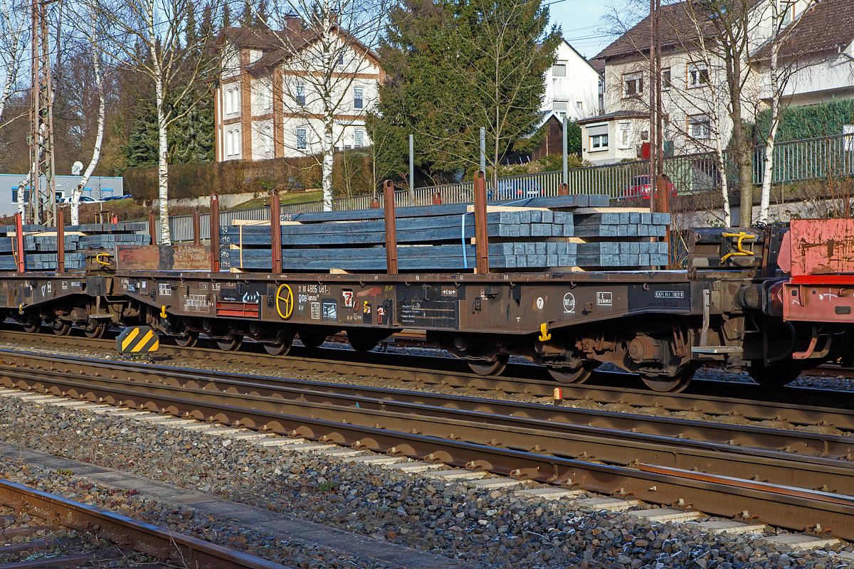 Sechsachsiger Drehgestell-Flachwagen, mit Rungen, Stirnwandklappen und klappbaren Ladeschwellen, jedoch ohne Seitenwandklappen, 31 80 4865 081-2 D-DB, der Gattung Samms 709, beladen mit Stahlkn�ppel (Vierkantstangen), am 22.12.2021 im Zugverband bei einer Zugdurchfahrt in Kreuztal. Hier im Bild sind je L�ngsseite 4 Rungen eingesteckt, je 2 Rungen lagern in Taschen an den Au�enlangtr�gern (hier im Bild links vom Handrad der Festellbremse).

Der Wagen dient mit aufgeklappten Ladeschwellen zur Bef�rderung von schweren Walzprofilen und anderen sperrigen G�tern. Mit eingeklappten Ladeschwellen, also mit ebener Ladeebene, eignen sich die Wagen mit dem Nummernkreis 31 80 4865 000-2 bis 999-5 auch zum Transport schwerer Kettenfahrzeuge. F�r das Be- und Entladen dieser Fahrzeuge sind befahrbare Stirnwandklappen und Abst�tzungen vorhanden. Bei den �brigen Wagen dieser Bauart wurden die Abst�tzungen stillgelegt.Wobei hier im Bild sind die Ladeschwellen eingeklappt, stattdessen wurden Vierkanth�lzer auf den flachen Wagenboden untergelegt.

Die Wagenbr�cke ist eine in Rahmenbauweise ausgef�hrte Schwei�konstruktion, deren Hauptbauteile aus St 52 bestehen. Die Hauptbelastungen werden von den �u�eren Langtr�gern aus IPE 600 aufgenommen. Die Puffertr�ger sind so ausgebildet, dass sp�ter ohne gro�e �nderungen die AK eingebaut werden kann.

Der Fu�boden besteht aus Kiefernbohlen mit den Abmessungen 70 x 200 mm; er kann eine Radlast von 5,0 t aufnehmen. Im Fu�boden sind 6 geteilte klappbare Ladeschwellen eingebaut. Das Fahrzeug hat auf jeder L�ngsseite 6 Einsteckrungen und an jeder Stirnseite je 2 versenkbare Rungen (Fallrungen). Die Stirnwandklappen sind umlegbar. Die Einsteckrungen lagern, wenn sie nicht gebraucht werden, in Taschen an den Au�enlangtr�gern. Die abgesenkten Fallrungen liegen noch innerhalb des Umgrenzungsprofils, so dass der Wagen auch mit abgesenkten Fallrungen und umgelegten Stirnwandklappen gefahren werden kann. Die Wagen sind mit einer bodenbedienbaren Feststellbremse ausger�stet. 

TECHNISCHE DATEN:
Gattung: Samms 709 (Gattungskennzahl 4865)
Erstes Baujahr: 1977
Spurweite: 1.435 mm (Normalspur)
L�nge �ber Puffer: 16.400 mm
Drehzapfenabstand: 9.150 mm
Radsatzstand in den Drehgestellen: 2 x 1.700 mm = 3.400 mm
Drehgestell-Typ: BA 711.5
Ladel�nge: 15.000 mm
Ladebreite: 2.585 mm (zwischen den Rungen)
Fu�bodenh�he �ber SO: 1.200 mm
Ladefl�che: 46 m�
Eigengewicht: 30.360 kg
Zuladung bei Lastgrenze S: 74,5 t (ab Streckenklasse D)
Zuladung auf DB Netz bei Streckenklasse CE/D: 89.5 t (max.100 km/h)
Max. Zuladung: 101,5 t
Max. Geschwindigkeit: 100 km/h (beladen) / 120 km/h (leer)
Kleinster Gleisbogenhalbmesser: 75 m
Bauart der Bremse: KE-GP (LL) 
Bremssohle: IP 116
Handbremse: Ja
Internationale Verwendungsf�higkeit: RIV
