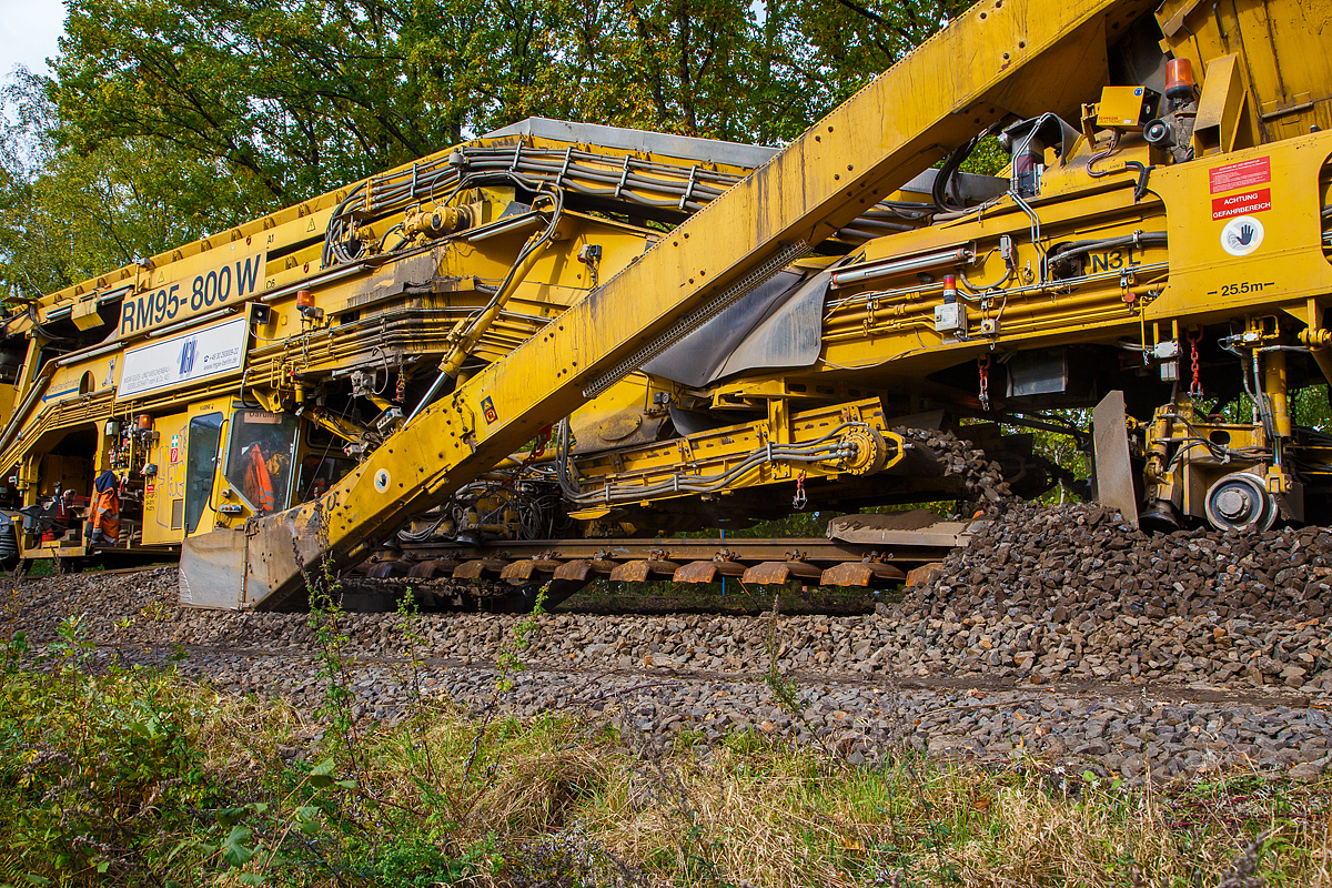 
Unter dem Gleis hindurch geschaut....
Detailbild vom Schotteraushub und ca. 2m dahinter (links) die Schotterrückführung (recycelt) der Plasser & Theurer Bettungsreinigungsmaschine RM 95-800 W der MGW Gleis- und Weichenbau-Gesellschaft mbH & Co. KG (Berlin), die auf der Hellertalbahn (KBS 462) im Einsatz ist, hier am 20.10.2020 in Neunkirchen-Altenseelbach.
