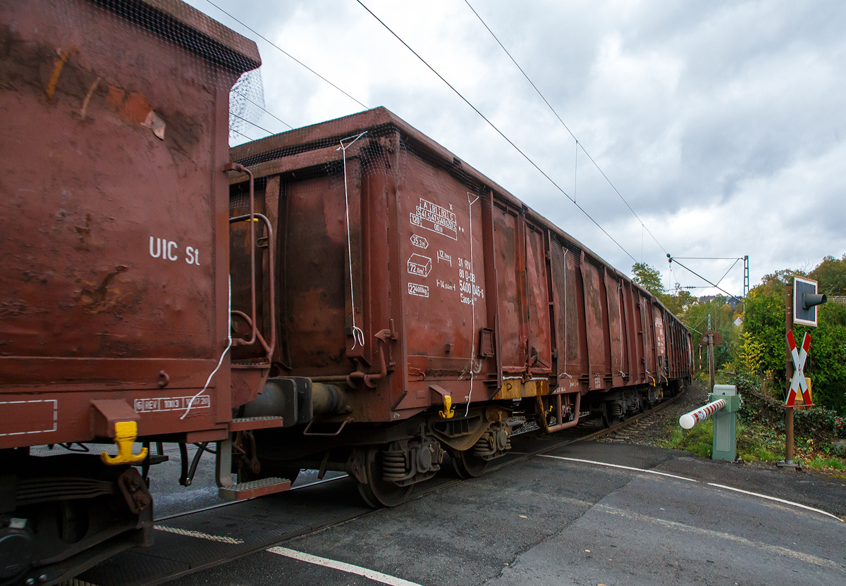 Vierachsiger offener Drehgestell-Güterwagen 31 80 5400 045-6, der Gattung Eanos-x 057, der DB Cargo AG am 22.10.2021 im Zugverband bei einer Zugdurchfahrt in Kirchen (Sieg), hier beim BÜ km 121,192.

Der Eaos-x 057 entstanden 1999 bis 2003 durch Festlegung der Stirnklappen an Eas 066-Wagen (ex DR Eas). Vorgesehen war zunächst die Umrüstung von 1.000 Wagen, die als stirnkippfähige Fahrzeuge nicht mehr benötigt wurden. Damit sollen Einsparungen für die Stirnklappen-Unterhaltung erzielt werden. Hier sieht man sehr gut dass die Stirnklappe verschweißt wurde.

Gebaut wurden diese Wagen 1981/82 von den französischen Herstellern Arbel-Fauvet-Rail und ANF-Industrie für die DR. Es waren die ersten offenen Drehgestellwagen nach UIC-Standard in der DDR.

Die ersten etwa 500 Fahrzeuge behalten bei der Umrüstung ihre jeweils zwei Doppeltüren je Wagenseite, bei allen folgenden Serien wird auf beiden Wagenseiten auf eine dieser Türen verzichtet, d.h. diagonal gegenüberliegende Türen sind entfernt und die Ausschnitte mit Blechen verschlossen. Ab etwa 2002 werden weitere 650 Eas 066 zu Eaos-x 057 umgerüstet. 

TECHNISCHE DATEN:
Spurweite: 1.435 mm (Normalspur)
Achsanzahl: 4 in zwei Drehgestellen
Länge über Puffer: 14.040 mm
Drehzapfenabstand: 9.000 mm
Achsabstand im Drehgestell: 1.800 mm
Ladelänge: 12.800 mm
Ladebreite:  2.760 mm
Ladehöhe: 2.100 mm
Ladefläche: 35,3 m²
Laderaum:  72,0 m³
Türöffnung: 2 Stück 1.800 × 1.900 mm
Höchstgeschwindigkeit: 100 km/h (beladen) / 120 km/h (leer)
Maximales Ladegewicht ab Streckenklasse C: 57,5 t 
Eigengewicht: 22.400 kg
Kleinster bef. Gleisbogenradius: R 35 m
Bremse: KE-GP (LL)
Handbremse: Teilweise Fbr.
Intern. Verwendungsfähigkeit: RIV