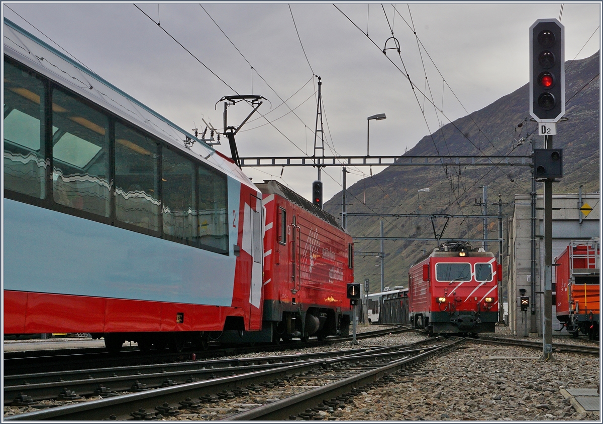 Während die HGe 4/4 des  Disentiser -Zuges in Andermatt rangiert, bzw. ihren Zug umfährt, wartet eine weiter HGe 4/4 mit ihrem Regionalzug 557 auf die Abfahrt nach Visp.
21. Okt. 2017