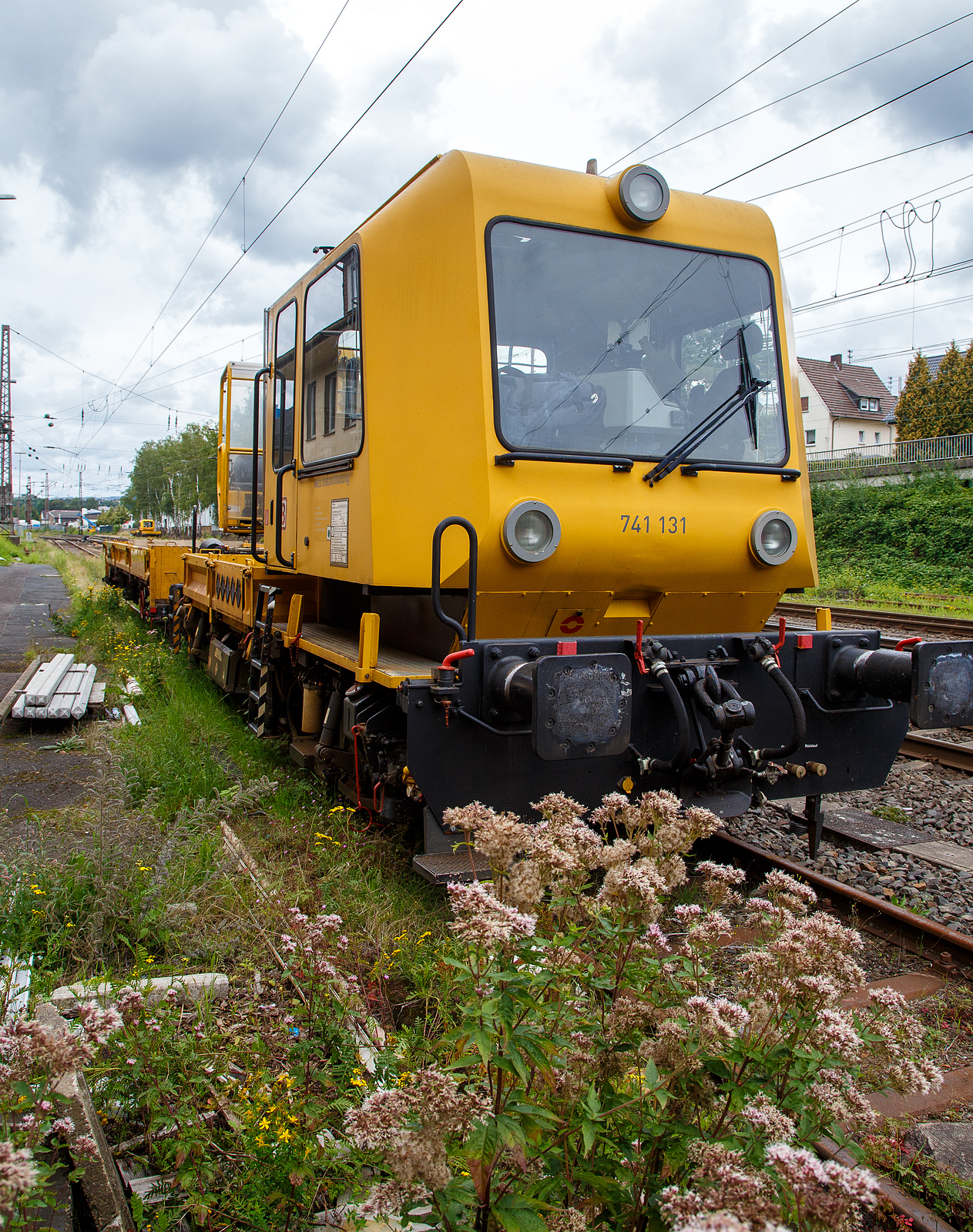 DB 741 131 ein Gleisarbeitsfahrzeug GAF 100 R (Schweres Nebenfahrzeug Nr. 99 80 9420 037-0, ex 97 17 50 011 18-3), mit dem Gleiskraftwagenanhänger H27, Schweres Nebenfahrzeug Nr. D-DB 99 80 9750 276-4 (Anhängerfahrzeug BR 771 725) beide von der DB Netz AG, sind am 13.08.2023 in Kreuztal abgestellt. Da ich kein Fabrikschild finden konnte, kann ich keine ehemalige Nr. zuordnen.

Das GAF 100 R wurde 1996 von GBM (Gleisbaumechanik Brandenburg/H. GmbH) unter der Fabriknummer 52.1.124 gebaut, es hat die EBA Nummer EBA 96 P01 N023.

Das Gleisarbeitsfahrzeuge GAF 100 R ist ein Nebenfahrzeug das von der Firma GBM Gleisbaumechanik Brandenburg/H. GmbH gebaut wurde. Mit ihm können Personen (zur Mitfahrt sind 6 Personen zugelassen), Material und Ausrüstungen befördert werden können. Zudem hat es einen Palfinger PK 9001 Kran.

Der Antrieb des zweiachsigen Fahrzeuges erfolgt von einem 6 Zylinder, wassergekühlten MAM D 0826 LOH 07 Dieselmotor mit 169 kW (230 PS) Leistung über Lastschaltwendegetriebe auf die Radsatzgetriebe.

Technische Daten GAF:
Achsfolge: B
Länge über Puffer: 9.100 mm
Achsabstand: 4.800 mm
Treibraddurchmesser: 750 mm (neu)
Höchstgeschwindigkeit: 100 km/h
Eigengewicht: 16 t
Zul. Anhängelast: 40 t / (80 t mit Regelzugeinrichtung Hg 60 km/h)
Nutzlast : 5,0 t
Zur Mitfahrt zugel. Personen: 6
Der Antrieb des zweiachsigen Fahrzeuges erfolgt von einem 6 Zylinder, wassergekühlten MAN D 0826 LOH 07 Dieselmotor mit 169 kW (230 PS) Leistung über Lastschaltwendegetriebe auf die Radsatzgetriebe.

Der H 27 (Anhänger zu GAF 100) wurde von der GBM (Gleisbaumechanik Brandenburg/H. GmbH) gebaut.

Der GBM beschreibt dieses Fahrzeug wie folgt:
Der Anhänger H 27 wurde im Zusammenhang mit den Nebenfahrzeugen der Gleisbaumechanik Brandenburg entwickelt und ist in Ladeflächenhöhe, Kupplungsausführung sowie Energie - und Pneumatikanschlüssen diesen angepasst. Eine Anpassung an weitere Gerätesysteme ist nach Kundenwunsch möglich. Der Anhänger H 27 dient dem Transport von Baumaschinen, er ist aber auch gut für das Transportieren von Stückgut, Kleinteilen und Schienen geeignet. Der H 27 ist mit einem Paar einhängebarer Auffahrrampen ausgerüstet. Die Montage der Auffahrrampen kann mit 2 Personen realisiert werden. In seinen Abmessungen erfüllt er die Anforderungen nach EBO, Anlage 8. Der H 27 hat eine Spurweite von 1.435 mm. Der Fußboden des H 27 ist so dimensioniert, daß ein Befahren mit Gabelstaplern mit einer Radlast von 30 kN möglich ist. Zu den Fahrzeugenden hin ist der Fußboden geneigt ausgeführt. Dadurch verringert sich die Fußbodenhöhe von 1.000 mm über Schienenoberkante im mittleren Bereich auf 700 mm über Schienenoberkante. Durch angelegte Auffahrrampen ist es möglich, auf den H 27 mit Baumaschinen zu fahren.

Technische Daten Gleiskraftwagenanhänger:
Achsanzahl: 2
Achsabstand: 6.000 mm
Länge über Puffer: 9.750 mm
Höchstgeschwindigkeit: 100 km/h (vorgestellt 80 km/h)
Eigengewicht: 9,3 t
Zul. Anhängelast: 40 t
Nutzlast : 25,0 t