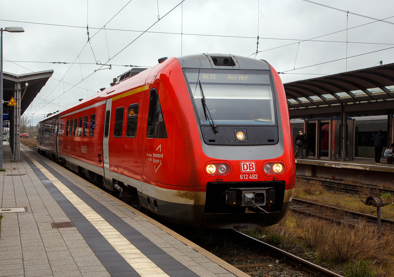 Der Dieseltriebwagen mit Neigetechnik 612 482 / 612 982 (95 80 0612 482-9 D-DB / 95 80 0612 982-8 D-DB), ein Bombardier  RegioSwinger  der DB Regio Bayern, hat als RE 35 „Main-Saale-Express“ (Bamberg – Lichtenfels –Hof), am 17.04.2023 seinen Zielbahnhof Hof erreicht.

Der Triebzug wurde 2003 von Bombardier unter den Fabriknummer 24173 und 24174 gebaut.

Die Fahrzeuge der Baureihe 612 sind Neigetechnik-Nahverkehrsdieseltriebwagen der Deutschen Bahn. Die Fahrzeuge werden vor allem als Regional-Express und Interregio-Express auf bogenreichen Strecken eingesetzt. Der Hersteller Bombardier Transportation bezeichnet die Fahrzeuge als RegioSwinger.

Der VT 612 ist ein zweiteiliger Dieseltriebzug mit Neigetechnik und dieselhydraulischen Antrieb. Die Neigetechnik erlaubt das bogenschnelle fahren. Durch das bogenschnelle fahren kann die Geschwindigkeit im Vergleich zu „herk�mmlichen“ Schienenfahrzeugen in kurvenreichen Strecken wesentlich erh�ht werden, da sich das Fahrzeug bis zu 8 Grad neigen kann. �hnlich wie ein serpentinenpassierender Motorradfahrer durchf�hrt der Zug die Kurve, was erhebliche Fahrzeitverk�rzung m�glich macht. Voraussetzung hierf�r ist jedoch nicht nur die Fahrzeugtechnik, sondern auch umfangreiche technische Anpassungen an den Gleis- und Signalanlagen entlang der Strecke und den Bahnh�fen.

Nach den problembehafteten Triebwagen der Reihe 611 unternahm die Deutsche Bahn mit der fast komplett neu konstruierten Baureihe 612 einen zweiten Versuch, einen zuverl�ssigen Neigetechnik-Zug aus deutscher Produktion auf die Schiene zu bringen.

Wie bei ihren Vorg�ngern sind bei der Baureihe 612 beide Wagen motorisiert. Verwendet werden dabei 19-Liter-Cummins- Sechszylinder-Reihenmotor-Dieselmotoren des Typs QSK19-R mit je 563 kW Leistung, die eine Geschwindigkeit von 160 km/h erm�glicht. Die Kraft�bertragung erfolgt hydraulisch �ber je ein Str�mungsgetriebe, in das au�erdem eine hydrodynamische Bremse integriert ist. Die Triebdrehgestelle liegen bei beiden Wagen einer Einheit am Kurzkuppelende, die Drehgestelle unter den F�hrerst�nden sind Laufdrehgestelle. Der Wagenkasten st�tzt sich �ber Luftfedern und eine Wiege auf den Drehgestellen ab und ist elektrisch 8� zu jeder Seite neigbar. Die Steuerung der Neigetechnik �bernimmt das System Neicontrol-E, das �ber Beschleunigungssensoren in den Enddrehgestellen Beginn und Ende eines Bogens feststellen kann und den Wagenkasten abh�ngig von Bogenradius und Fahrgeschwindigkeit neigt. Dies erlaubt gegen�ber Fahrzeugen ohne Neigetechnik eine Geschwindigkeitssteigerung um bis zu 30 %, sofern die befahrene Strecke sicherungs- und oberbautechnisch f�r das bogenschnelle Fahren ausgebaut ist. Zus�tzlich zu den Betriebsbremsen besitzen die Triebwagen Federspeicherbremsen als Feststellbremsen und f�r Schnellbremsungen Magnetschienenbremsen in den Laufdrehgestellen.

�ber die selbstt�tigen Scharfenberg-Kupplungen an den F�hrerstandsenden lassen sich bis zu vier Doppeltriebwagen kuppeln und vielfachsteuern. Die Scharfenberg-Kupplungen verbinden die Druckluft- und Steuerleitungen selbstt�tig mit. Die Bordrechner der Triebz�ge stellen automatisch die Zugkonfiguration fest. F�r die Aufrechterhaltung gewisser Grundfunktionen wie Beleuchtung und Heizung ist jeder Triebwagen selbst verantwortlich. Es kann nicht in gr��erem Umfang elektrische Energie zwischen den Wageneinheiten ausgetauscht werden. �ber die Vielfachsteuerung gelangen Zustands- und St�rungsmeldungen zum aktiven F�hrerstand.

TECHNISCHE DATEN:
Spurweite: 1.435 mm (Normalspur)
Achsformel: 2’B’+ B’2’
L�nge �ber Kupplung (Scharfenberg): 51.750 mm
Achsabstand im Drehgestell: 2.450 mm
H�he: 4.124 mm
Breite: 2.852 mm
Treibrad- und Laufraddurchmesser: 890 mm
Eigengewicht: 93 t
Dienstgewicht: 116 t
Motorleistung: 2x 560 kW
H�chstgeschwindigkeit: 160 km/h
Sitzpl�tze: 146
Fu�bodenh�he: 1.290 mm
