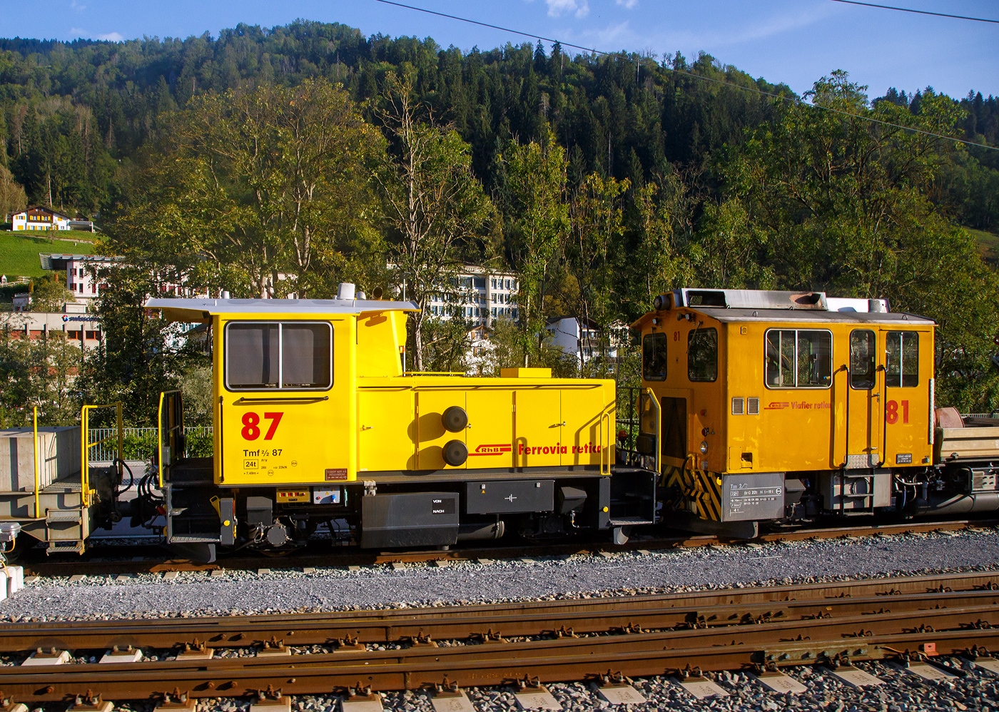 Der nun gelbe  Refit   Traktor (Surselva) RhB Tmf 2/2 87 abgestellt 07 September 2021 beim Bahnhof Castrisch (aufgenommen aus einem Zug heraus). 

Auch er wurde die im Rahmen des Projekts «Refit Baudienstfahrzeuge Tm(f) 2/2» im Jahr 2020 umgebaut.

Die Tmf 2/2  87 wurde 1992 von RACO (Robert Aebi AG, Regensdorf, Schweiz) unter der Fabriknummer 1988 gebaut und an die RhB geliefert. Die RACO Typenbezeichnung ist 420 CT 4H. Im Jahr 2020 erfolgte dann der Umbau.

Zu immer höheren Unterhalts- und Revisionskosten führen nach den Jahren im Betrieb einige Komponenten aus dem Antriebsstrang und dabei vor allem der Cummins-Dieselmotor. Aufgrund seines Alters kann dieser Motorentyp nicht mehr als Neuteil beschafft, sondern nur noch revidiert werden.

Aus diesem Grund hat sich die RhB vor einigen Jahren entschieden, diesen Dieselmotor bei den Tmf 2/2 85-90 zu ersetzen. Nach umfangreichen Untersuchungen wurde bald klar, dass nebst dem Dieselmotor auch einige andere zentrale Fahrzeugkomponenten von Obsoleszenz betroffen sind und weitestgehend nicht mehr den heutigen technischen Ansprüchen genügen. Dazu gehören Getriebe, Partikelfilteranlage, Kühlungsanlage, Hydraulik, Pneumatik, Bremsmechanik wie aber auch die komplette elektrische Einrichtung, die Fahrzeugsteuerung, die Sicherheitseinrichtung und die Fahrdatenvisualisierung. Grob umschrieben in etwa alles außer dem Chassis, Kabine und Achsen.

Antriebsstrang:
Aufgrund der betrieblichen Anforderungen entschied die RhB, den Reihen 6-Zylinder durch einen V8-Dieselmotor von Deutz zu ersetzen. Der neue Motor ist dank seiner V-Bauweise sehr kompakt und kann je nach Drehzahl bis zu 30 % mehr Leistung abgeben als der bestehende. Um diese Leistung optimal auf die Schienen zu bringen, wurde das bestehende Lastschaltgetriebe durch ein automatisches Wendegetriebe der Firma Voith ersetzt. Dieses Getriebe sowie auch die komplette Kühlanlage wurden von Voith auf die Leistungsdaten des Motors optimal abgestimmt. Ein großer Benefit nebst der Leistungssteigerung und der „Einfachheit“  des Antriebsstranges liegt darin, dass die Gangschaltung – mit welcher die restlichen Tmf  2/2 gestraft sind – nicht mehr von Relevanz ist. Dank dem neuen Automatikgetriebe lässt sich die Geschwindigkeit stufenlos und ohne Leistungseinbruch zwischen V null und V max. einstellen.

Fahrzeugsteuerung und Fahrdatenvisualisierung
Die bestehende KraussMaffei-Fahrzeugsteuerung wurde durch eine von Selectron, die RhB-Standard ist, ersetzt. Die Antriebsstrangkomponenten (Dieselmotor / Getriebe) wie auch Fahrzeugkomponenten wie beispielsweise Display, Funkfernsteuerung usw. kommunizieren über einen Fahrzeugbus mit der Fahrzeugsteuerung. Dadurch erleichtert sich die Fehlerdiagnose und es konnten viele elektromechanische Komponenten eingespart werden. Die Fahrzeugdaten werden dem Lokführer über Displays visualisiert.

TECHNISCHE DATEN der RhB Tmf 2/2 (Refit):
Baujahre: 1991/92 und 1994
Spurweite: 1.000 mm (Meterspur)
Achsfolge: B
Länge über Puffer:  7.490 mm
Achsabstand: 3.750 mm
Breite: 2 700 mm
Eigengewicht:  24 t
Höchstgeschwindigkeit: 60 km/h (60 km/h Schleppfahrt)
Treibraddurchmesser:  750 mm
Motorentyp: Deutz V8-Dieselmotor 
Weitere Daten wie auch Motor- und Getriebetyp sind mir leider noch unbekannt.

Vermutlicher Motor:
Wassergekühlter V8-Zylinder-Viertakt-Dieselmotor mit Abgasturbolader, Ladeluftkühlung und wassergekühlten Abgasrohre vom Typ TCD 2015 V8 mit einer Leistung von 440 kW bei Drehzahl 1.900 U/min.
Weitere Daten:
Bohrung: Ø132 mm
Hub:  145 mm
Hubvolumen: 15.9 l
Max. Nenndrehzahl: 2.100 U/min
Max. Drehmoment: 2.650 Nm bei Drehzahl 1.400 U/min
Länge: 1.006 mm
Breite: 932 mm
Höhe: 1.152 mm
Gewicht: 1.250 kg