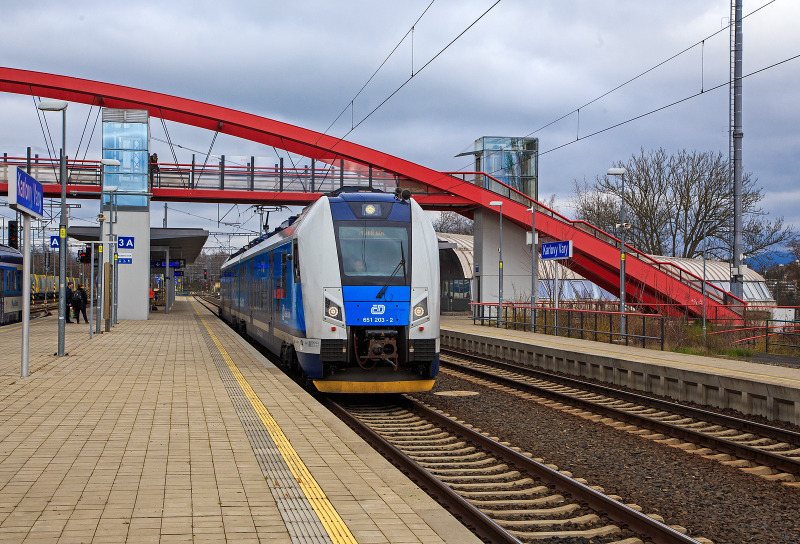 Der RegioPanter 651 203-2 / 650 203-3 (CZ-ČD 94 54 1 651 203-2  / CZ-ČD 94 54 1 650 203-3), ein zweiteiliger Zweisystem-Elektrotriebzug (3 kV DC und 25 kV, 50 Hz~) vom Typ ¦koda 15 Ev, der České dráhy (ČD) / Plzeňský Kraj (deutsch Pilsner Region) verlässt am 18.04.2023, als Sp nach Pilsen (Plzeň) via Cheb (Eger), den Bahnhof Karlovy Vary (Karlsbad oberer Bahnhof).

Der zweiteiliger zweisystemfähiger (3 kV DC und 25 kV, 50 Hz~) Elektrotriebzug vom Typ ¦koda 15Ev/HV14 wurde 2021 von ¦koda Vagonka a.s. in Ostrava (ex ČKD Vagónka Studénka) gebaut.

Die einstöckigen Elektrotriebzüge RegioPanter stellen eine völlig neue Generation von modernen Niederflur-Fahrzeugen dar. Sie werden mit einem Stromsystem (3 kV DC) und mit zwei Stromsystemen (3 kV DC und  25 kV / 50 Hz AC) bei der wie die hier gezeigten BR 650 / 651 angeboten. Die ČD hat zwei- und dreiteilige Einheiten bestellt, laut Hersteller sind bis zu sechsteilige Kompositionen möglich. Bis zu vier Wagenzüge sind kuppelbar. Die BR 650.2 / 651.2 werden als Typ ¦koda 15 Ev und sind gegenüber der BR 650.0 / 651.0 (¦koda 7 Ev) modifiziert. Beide Wagenteile sind jeweils mit einem Triebdrehgestell mit zwei Asynchronmotoren und einem üblichen Laufdrehgestell ausgestattet. Im Vergleich zu den vorhanden Zwei-Wagen-Zügen verbraucht der Zug RegioPanter bis um eine Hälfte  weniger Strom, und zwar auch dank des Systems der Energierückgewinnung, die beim Bremsen entsteht. Die einstöckige regionale Einheit ist als ein völlig durchgängiger Zug konzipiert, d.h. ohne Innenzwischenwände und Türen.  Offen ist auch der Übergang zwischen den Wagen. Die meiste elektrische Ausrüstung befindet sich auf dem Dach, wodurch sich der Fahrgastraum erheblich erweitert. Die Drehstrom-Traktionsmotoren vom Typ ¦koda ML 3942 K/4 besitzen eine Leistung von je 340 kW.

TECHNISCHE DATEN:
Spurweite: 1.435 mm
Achsformel: Bo‘2‘+2‘Bo‘
Länge über Kupplung: 52.900 mm
Breite: 2.820 mm
Höhe: 4.260 mm
Drehzapfenabstand: 19.000 mm
Achsabstand im Drehgestell: 2.400 mm
Raddurchmesser: 850 (neu) / 770 mm (abgenutzt)
Dauerleistung: 1.360 kW (4 x 340 kW)
Höchstgeschwindigkeit: 160 km/h 
May. Beschleunigung: 1,1 m/s²
Stundenzugkraft: 131 kN
Kleinster befahrbarer Gleisbogen: 125 m
Stromsystem: 3 kV DC und  25 kV / 50 Hz AC
Leergewicht: 102,8 t
Anzahl der Sitzplätze: 140, davon  8 in der 1. Klasse
Anzahl der Stehplätze: 183
Plätze für Fahrräder/Kinderwagen: 9 / 4
