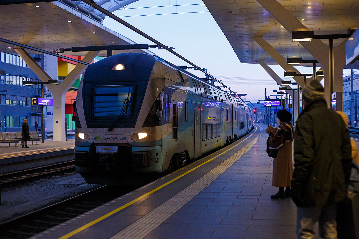 Der sechsteilige Stadler Kiss³ 4010 120 bis 4010 620 der WESTbahn fährt als west 907 (St. Johann im Pongau - Bischofshofen - Salzburg Hbf - Attnang-Puchheim - Linz Hbf- St. Pölten Hbf - Wien Westbahnhof) am 14 Januar 2025 pünktlich um 07:43 Uhr in den Hauptbahnhof Salzburg ein. Wir fahren bis Attnang-Puchheim mit.

Die WESTbahn (WESTbahn Management GmbH, Österreich unterhält seit 2011 im Open Access den Intercitybetrieb vor allem zwischen Wien und Salzburg mit Doppelstocktriebzügen des Typs KISS, aber auch von Salzburg über Innsbruck nach Lindau Insel oder über München nach Stuttgart. Dank der sehr hohen Verfügbarkeit der Züge erreicht die WESTbahn im Wettbewerb sehr gute Pünktlichkeitswerte und genießt hervorragende Passagierzahlen. Die WESTbahn bestellte im Oktober 2019 bei Stadler 15 weitere Kompositionen
als Ersatz für die 17 bestehenden Fahrzeuge (acht sechsteilige und neun vierteilige KISS), die an die Deutsche Bahn Fernverkehr AG verkauft wurden. 

Stadler liefert insgesamt 15 sechsteilige Kompositionen. Die neuen Doppelstock-Triebzüge sind je 150 Meter lang. Der Komfort entspricht in allen Wagen dem Standard der First-Klasse und im Endwagen 600, auf Grund der
2+1-Bestuhlung, der Plus-Klasse. Durch die druckertüchtigte Ausführung, einer neu integrierten Brandmeldeanlage und einem weiteren Drehgestell-Upgrade wird der Komfort weiter gesteigert und der geplanten Streckenerweiterung nach Deutschland und eventuell auch in die Schweiz steht nichts im Wege. Alle Mittelwagen sind mit einem modernen Bistro ausgerüstet, wo sich
die Reisenden verpflegen können. Ebenfalls stehen in allen Mittelwagen getrennte Toiletten (Damen/Herren) und im Mittelwagen 400 ein PRM-WC zur Verfügung. Während der Fahrt wird den Fahrgästen durch die mitfahrenden Stewards ein umfassender Rundum-Service geboten. Die Züge erreichen eine Höchstgeschwindigkeit von 200 km/h. Die Auslieferung der neuen Fahrzeuge
an die WESTbahn fand im Jahre 2021 statt. 

TECHNISCHE DATEN der KISS³:
Anzahl: 15 sechsteilige Triebzüge
Spurweite: 1.435 mm (Normalspur)
Achsformel: Bo’Bo’+2’2’+2’2’+2’2’+2’2’+Bo’Bo’
Länge über Kupplung: 150.000 mm
Fahrzeugbreite: 2.800 mm
Fahrzeughöhe: 4.595 mm
Achsstand im Drehgestell: 2.500 mm (Trieb- und Laufdrehgestell)
Trieb- und Laufraddurchmesser:  920 mm (neu)
Dauerleistung am Rad: 4.000 kW
Max. Leistung am Rad: 6.000 kW
Anfahrzugskraft (bis 68 km/h): 320 kN
Anfahrbeschleunigung: 0.85 m/s²
Höchstgeschwindigkeit 200 km/h
Sitzplätze: 521, davon 13 Klappsitze (First 34, Comfort 106, Standard 368)
Stehplätze: 758
Stromsystem: 15 kV AC, 16.7 Hz
Fußbodenhöhe: Niederflur am Einstieg 570 mm, Unterdeck 440 mm, Oberdeck 2.515 mm
Einstiegsbreite: 1.400 mm
Speisespannung 15kVAC, 16.7Hz