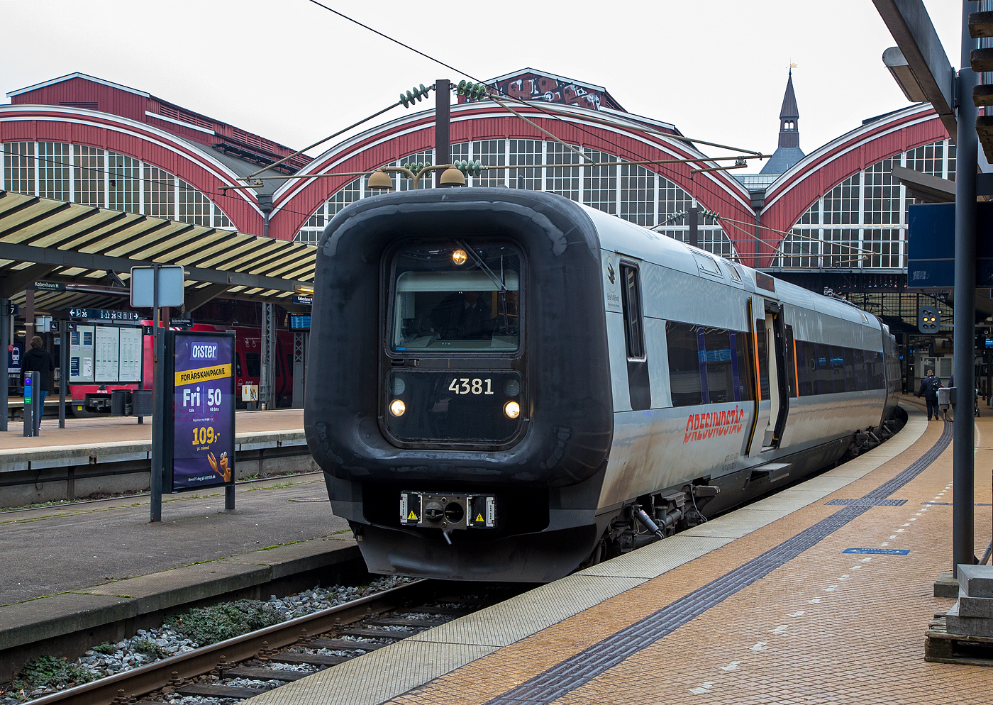 Der Transitio X31K 4381 (M4381, T4781 und M4581, bei DSB ET-FT-ET), ein ADtrnaz/Bombardier Crusalis Contessa, verl�sst am 20 M�rz 2019 als �resundstog (schwedisch �resundst�g) den Hauptbahnhof Kopenhagen (K�benhavns Hovedbaneg�rd). 

Der dreiteilige Elektrotriebzug wurde 2008 von Bombardier gebaut und an die d�nische DSB als ET-FT-ET 4381 geliefert, 2011 ging er an die schwedische AB Transitio. Die heutigen UIC-Nummern sind 94 74 4314 381-5 S-ABTR / 94 74 4314 781-6 S-ABTR / 94 74 4314 581-0 S-ABTR.

Der SJ X31K ist ein schwedischer dreiteiliger Elektrotriebzug der von Adtranz (sp�ter Bombardier), als Crusalis Contessa f�r die SJ (Statens J�rnv�gar) gebaut wurde. In D�nemark hat der Zug die Baureihenbezeichnung ET. Der Kennbuchstabe K bedeutet, dass die Triebz�ge f�r den Verkehr nach und in D�nemark angepasst sind, d.h. es sind Zweisystem-Triebz�ge die in Schweden (15 kV 16⅔ Hz) und D�nemark (25 kV 50 Hz) unterschiedlichen elektrischen Systeme. Beide L�nder haben unterschiedliche Zugbeeinflussungseinrichtungen und Signalsysteme. Die Umschaltung zwischen den beiden Systemen erfolgt w�hrend der Fahrt auf Peberholm. 

Die Triebz�ge werden haupts�chlich im �resundst�g-Verkehr in der Relation der St�dte Helsing�r–Kopenhagen–Malm� und dar�ber hinaus nach �ngelholm, G�teborg, H�ssleholm, Kalmar und Karlskrona eingesetzt. Die X31 verkehren auch als InterCity-Zug auf der V�stkustbana unter der Regie von Statens J�rnv�gar (SJ). Etwa die H�lfte der Z�ge geh�rt den Danske Statsbaner (DSB) und werden unter der d�nischen Baureihenbezeichnung ET gef�hrt, den Rest betreiben verschiedene schwedische Betreiber f�r die Gesellschaft �resund AB.

Die Triebz�ge sind rund 79 Meter lang und haben ein Leergewicht von etwa 156 Tonnen. Jeder Zug besteht aus zwei angetriebenen End- sowie einem antriebslosen Mittelwagen, der die Stromabnehmer und die Hochspannungsdachausr�stung tr�gt und verf�gt �ber insgesamt 229 Sitzpl�tze, davon 20 Sitzpl�tze in der 1. Klasse sowie 31 Klappsitze. In dem Dreiwagenzug tr�gt jeder Wagen eine eigene Nummer, wobei die Endziffern �bereinstimmen: 43xxhat einen F�hrerstand, 47xx ist der Mittelwagen und 45xx hat einen F�hrerstand und ein Erste-Klasse-Abteil.

Die Wagenk�sten haben eine Breite von 2,97 m und wurden aus wartungsfreiem Edelstahl gefertigt. Sie besitzen eine hellgraue Farbgebung, um optisch zu den d�nischen Triebwagen aus Aluminium zu passen. Die Frontseiten sind durch die breiten Gummiw�lste schwarz. Bis zu f�nf Einheiten k�nnen miteinander gekuppelt und in Mehrfachtraktion gefahren werden. Die Frontt�ren mit F�hrerstand k�nnen seitlich weggeschwenkt werden, damit besteht freier Durchgang durch den gesamten Zug. Dies ist eine Sicherheitsanforderung bei der Fahrt durch den Drogdentunnel als Teil der �resundverbindung. Weitere Sicherheitsanforderungen sind die Notbrems�berbr�ckung, eine Grundvoraussetzung f�r Z�ge auf der �resundverbindung und im Citytunnel Malm�. Auf der �resundverbindung ist nicht wie sonst in Schweden der Triebfahrzeugf�hrer f�r die Sicherheit der Passagiere verantwortlich, ohne Bordpersonal gelten die d�nischen Vorschriften.

Der elektrische Triebzug speist beim regenerativen Bremsen wieder Strom in die Oberleitung ein. Die H�chstgeschwindigkeit liegt bei 180 km/h. Acht der zw�lf Achsen eines Triebzuges sind mit Asynchronmotoren angetrieben, was bei einer maximalen Leistung von 2.300 kW zu guten Beschleunigungswerten f�hrt. Der Mittelwagen l�uft auf zwei Laufdrehgestellen.Die Triebgestelle weisen einen Achsstand von 2.600 mm und sind mit zwei Fahrmotoren ausgestattet. An den Radscheiben der Triebdrehgestelle sind die Bremsscheiben der Scheibenbremsen angebracht. Drei der vier Triebdrehgestelle besitzen zudem eine Magnetschienenbremse.

TECHNISCHE DATEN:
Spurweite:  1.435 mm (Normalspur)
Achsformel: Bo’Bo’+2’2’+Bo’Bo’
L�nge �ber Kupplung: 78.900 mm 
H�he: 3.800 mm
Breite: 2.966 mm
Eigengewicht: 156 t 
H�chstgeschwindigkeit: 180 km/h
Dauerleistung: 2.300 kW  (8 x 287,5)
Anfahrzugkraft: 170 kN
Anzahl der Fahrmotoren:8
Stromsystem: 25 kV 50 Hz und 15 kV 16⅔ Hz
Sitzpl�tze:  20 (1. Klasse) / 178 (2. Klasse) und 31 Klappsitze
Kupplungstyp: Scharfenbergkupplung