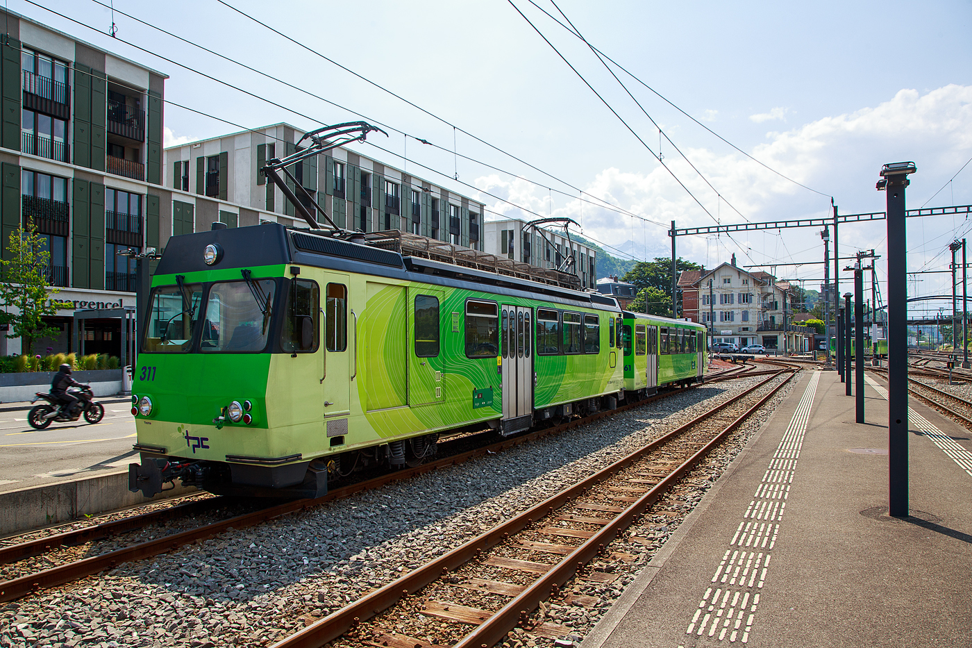 Der Triebwagen mit Gep�ckabteil BDeh 4/4 311 (ex 303)  „Yvorne“ und der Steuerwagen Bt 361 (ex 353) beide der tpc (Transports Publics du Chablais), ex bzw. Betriebsteil AL - Aigle-Leysin-Bahn, stehen am 28 Mai 2023 im Schmalspur-Bahnhof Aigle. Auch dieser Pendelzug tr�gt nun die neue TPC-Lackierung und nicht mehr die urspr�ngliche Lackierung der AL (creme-braun), nach der Neulackierung wurden auch nicht mehr die Wappen der Triebwagen angebracht.

Der Trieb- und Steuerwagen wurde 1987 von Vevey - Ateliers de constructions m�caniques de Vevey (ACMV) gebaut, die SLM (Schweizerischen Lokomotiv- und Maschinenfabrik) in Winterthur lieferte die Drehgestelle mit der Zahnradtechnik und die BBC (Brown, Boveri & Cie.) die elektrische Ausr�stung. Die ehemalige Fabrikhalle der ACMV steht heute noch in Vevey, siehe: http://hellertal.startbilder.de/bild/schweiz~hersteller~vevey-acmv-spaeter-vevey-technologies-sa/814732/die-ehemalige-fabrikhalle-des-1842-gegruendeten.html

Die Triebwagen BDeh 4/4 311 bis 313 (ex 303 bis 305) sind meterspurige elektrische Personentriebwagen mit Gep�ckabteil f�r gemischten Zahnrad- und Adh�sionsbetrieb (Zahnstangensystem Abt). Der Pendelzug (BDeh 4/4 mit Bt) besitzt nur die 2. Wagenklasse auf eine 1. Wagenklasse wurde verzichtet. 

Anfang der 1980er Jahren pr�sentierte sich das Rollmaterial der AL zwar in einem guten Zustand, doch gen�gte es den Komfortanspr�chen nur noch bedingt. Da auch die drei anderen Bahnen der TPC neues Rollmaterial ben�tigten, wurde ein gemeinsames Beschaffungskonzept erarbeitet. Schlie�lich fand im sechsten Rahmenkredit f�r Privatbahnhilfe des Bundes auch eine Rollmaterialbestellung f�r AL, AOMC und BVB Platz. 1984 wurden insgesamt drei neue Pendelz�ge f�r die AL (2 St�ck) und die BVB (1 St�ck) bei ACMV, SLM und BBC in Auftrag gegeben. Die bei der AL als BDeh 4/4 303-304 bezeichneten Fahrzeuge stellen eine Weiterentwicklung der BVB BDeh 4/4 81-82 dar und wurden mit 4 x 209 kW motorisiert. Wie die BDeh 4/4 301-302 haben sie eine Maximalgeschwindigkeit von 40 km/h, was aber f�r die AL-Verh�ltnisse gen�gt. Gleichzeitig mit den Triebwagen wurden 1987 auch zweipassende Steuerwagen Bt 353-354, die vom CEV Bt 223 abgeleitet wurden, in Betrieb genommen.

Mit den neuen Pendelz�gen hielt auch ein neues Erscheinungsbild bei der TPC Einzug. Die Fahrzeuge aller vier Eisenbahngesellschaften wurden in einheitlichem Design gestaltet, wobei die bahneigenen Farben beibehalten werden konnten (creme-braun f�r die AL). Ab 1989 hielt dieser Anstrich auch bei den �brigen Fahrzeugen der AL Einzug. 1993 wurde mit dem BDeh 4/4 305 und Bt 355 ein weiterer, praktisch baugleicher Pendelzug in Betrieb genommen.  Im Jahr 2002 erfolgte die Umzeichnung der Triebwagen BDeh 4/4  303 bis 305 in BDeh 4/4 311 bis 313, sowie der Steuerwagen Bt 353 bis 355 in Bt 361bis 363.

Auch wenn Triebwagen zusammen mit den Steuerwagen als Pendelz�ge konzertiert sind, so haben die Triebwagen trotzdem zwei F�hrerst�nde und k�nnen so auch alleine in beide Richtungen fahren.

TECHNISCHE DATEN:
Hersteller: (1987/1993) ACMV/SLM/BBC
Baujahr: 1987 (2 St�ck) / 1993 (1St�ck)
Spurweite: 1.000 mm
Fahrleitungsspannung: 1.500 V =
Maximale Streckenneigung: Adh�sion 38 ‰ / Zahnstange 230 ‰
Zahnstangensystem: Abt

TRIEBWAGEN:
Typ und Nummerierung: BDeh 4/4 311 – 313 (bis 2002 ex 303 bis 305)
Achsfolge: Bo'zz Bo'zz
L�nge �ber Puffer: 15.400 mm
Leistung: 4 x 209 kW = 836 kW (1.136 PS)
H�chstgeschwindigkeit: 40 km/h (Adh�sion) / 25 km (Zahnrad)
�bersetzung: 1:12,2
Gewicht: 35.8 t
Sitzpl�tze: 32
Stehpl�tze: 29
Max. Ladegewicht: k.A.

STEUERWAGEN:
Typ und Nummerierung: Bt 361–363 (bis 2002 ex Bt 353–355)
Anzahl der Achsen: 4
Gewicht: 10,0 t
Sitzpl�tze: 40
Stehpl�tze: 72