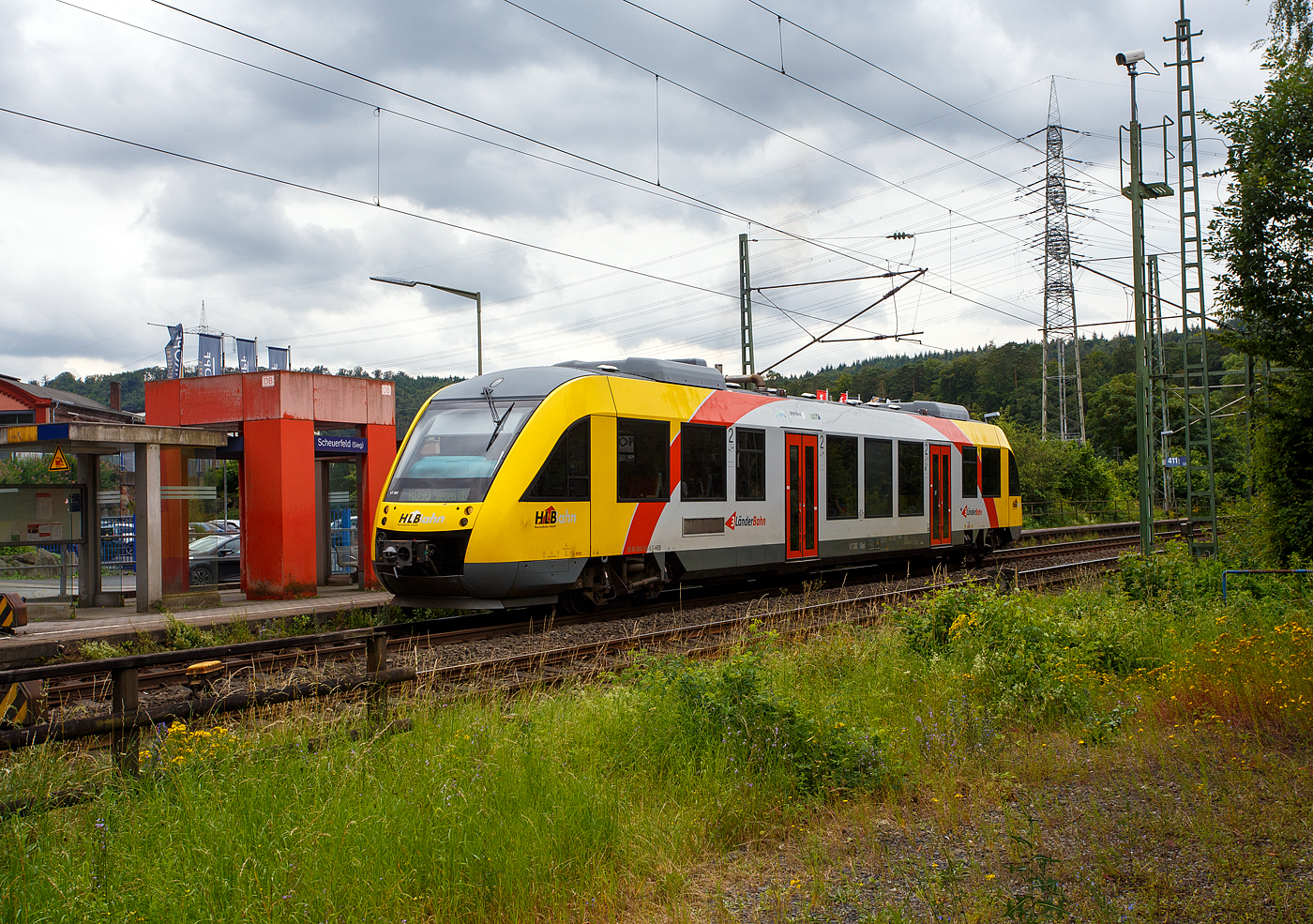 Der VT 202 ABpd (95 80 0640 102-9 D-HEB), ein Alstom Coradia LINT 27 der HLB, ex vectus VT 202, am 01 Juli 2024, als RB 90  Westerwald-Sieg-Bahn  Limburg/Lahn – Westerburg - Altenkirchen – Au/Sieg - Betzdorf/Sieg – Siegen (Umlauf HLB61718), beim Halt im Bahnhof Scheuerfeld(Sieg). 

Der Alstom Coradia LINT 27 wurde 2004 von Alstom (vormals Linke-Hofmann-Busch GmbH (LHB) in Salzgitter-Watenstedt unter der Fabriknummer 1187-002 gebaut und an die vectus Verkehrsgesellschaft mbH, mit dem Fahrplanwechsel am 14.12.2014 wurden alle Fahrzeuge der vectus nun Eigentum der HLB.

Der LINT (Leichter Innovativer Nahverkehrstriebwagen) war eine Entwicklung von Linke-Hofmann-Busch (LHB) in Salzgitter. Diese wurde 1994/1995 vom französischen GEC-Alstom-Konzern übernommen, wo der LINT innerhalb der CORADIA-Familie vermarktet wird, wobei sie immer noch in Salzgitter gebaut werden. Übrigens die Typenbezeichnung 27 stammt von der gerundeten Länge von 27,21 m. Die Baureihe 640 ist der kleinste Vertreter moderner Dieseltriebwagen hier zu Lande. Der einteilige Dieseltriebwagen der Baureihe 640 hat Mittelpufferkupplungen (Scharfenbergkupplung) vom Typ 10)und zwei Türen pro Fahrzeugseite.Es können mehrere Fahrzeuge zu einem Zugverband zusammengekuppelt werden.

Dieser einteilige VT wird von einem MTU 6R183TD13H Dieselmotor mit 315 kW (428 PS) Leistung angetrieben. Die Kraftübertragung erfolgt über ein dieselmechanisches Automatikgetriebe über Kardanwelle auf die  Achsgetriebe. Eine Besonderheit ist die dieselhydraulische Kraftübertragung bei den LINT 27 der DB Regio, während in allen anderen Nachfolgebaureihen (wie hier der HLB, ex vectus) ein dieselmechanisches Automatikgetriebe eingebaut wurde.

Als Bremsen werden druckluftbetätigte Scheibenbremsen verwendet, an je einem Triebdrehgestell befinden sich zusätzlich Magnetschienenbremsen. Als Feststellbremse sind Federspeicher vorhanden. Die Bremsanlagen ist von Knorr-Bremse. Die Fahrzeuge der HLB (wie auch die DB Regio) verwenden zudem Retarder als hydrodynamische Ergänzungsbremse. Die Fahrzeuge verfügen zusätzlich über Rußpartikelfilter.

Die Fahrzeuge verfügen über voneinander unabhängige Führerraumklimaanlagen und Fahrgastraumklimaanlagen. Je Wagenkasten sind zwei Dachklimageräte vorhanden. Die Abwärme der Dieselmotoren wird zur Beheizung von Fahrgasträumen und Führerräumen genutzt. Reicht die Abwärme nicht aus, so werden dieselbefeuerte Zusatzheizgeräte zugeschaltet. Geliefert wird die Heizungs-, Lüftungs-, Klimaanlage von „Spheros“ (ehemals Webasto).

Die Steuerschränke im Führerraum werden als Sonderlösung von Rittal produziert und von Alstom ausgerüstet.

TECHNISCHE DATEN:
Baureihenbezeichnung: 640
Hersteller:	Alstom Transport Deutschland GmbH
Spurweite: 1.435 mm (Normalspur)
Achsfolge: B’2’
Länge über Kupplung: 27.210 mm
Drehzapfenabstand: 18.450 mm
Achsabstand im Drehgestell: 1.900 mm
Höhe: 4.340 mm
Breite: 2.750 mm
Eigengewicht: 43,5 t
Dieselmotor: MTU 6R183TD13H (PowerPack Sechszylinder-Reihenmotor), ex Mercedes Benz OM 447 h LA
Leistung: 315 kW (428 PS)
Höchstgeschwindigkeit: 120 km/h
Beschleunigung:  0,5 m/s²
Bremsverzögerung: 0,9 m/s²
Sitzplätze: 	ca. 70
Fußbodenhöhe: 	580 mm (Einstieg), 598 mm (NF-Bereich), 1.160 mm (Hochflurbereich)
Fahrzeugbestand der HLB: 10

