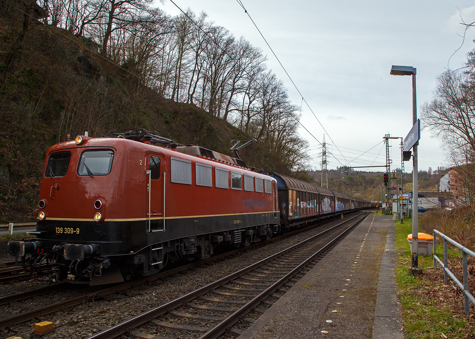 Die 139 309-9 (91 80 6139 309-9 D-BYB) der BayernBahn GmbH f�hrt am 28.03.2023, mit dem sogenannten  Henkelzug  (Langenfeld/Rhld. nach Gunzenhausen), durch Scheuerfeld (Sieg) in Richtung Siegen. Der Zug bestand aus gedeckten Schiebewand-Wageneinheiten der Gattung Hiirrs der TRANSWAGGON GmbH.

Nochmals einen lieben Gru� an den netten Lf zur�ck.

Die E 40.13 wurde 1964 bei Krauss-Maffei in M�nchen unter der Fabriknummer 18838 gebaut, der elektrische Teil ist von BBC (andere Quellen behaupten SSW, ich konnte aber BBC lesen). Nach dem verl�ngerten Fristablauf zum 01.07.2016, wurde sie zum 01.01.2020 an die Bayernbahn GmbH verkauft. Im Jahr 2016 konnte ich die Lok noch als DB Lok ablichten, siehe: http://hellertal.startbilder.de/bild/deutschland~unternehmen~db-cargo-ag-ex-db-schenker-rail-deutschland-ag/477736/wohl-eine-der-letzten-im-db-bestanddie.html  

Die Baureihe 139 sind vom Grunde her Lok der Baureihe 140 nur mit dem feinen aber wesentlichen Unterschied das sie eine elektrische Widerstandsbremse hat. Mit Ausnahme der anderen Getriebe�bersetzung sind sie fast identisch mit der E 10.1. Ab 1959 wurden 31 Lokomotiven speziell f�r den Einsatz auf den Steilstrecken Erkrath – Hochdahl, Altenhundem – Welschen-Ennest – (teilweise bis Kreuztal) und der H�llentalbahn beschafft.

TECHNISCHE DATEN:
Spurweite: 1.435 mm
Achsanordnung: Bo´Bo´
L�nge �ber Puffer: 16.490 mm
Drehzapfenabstand: 7.900 mm
Achsstand in den Drehgestellen: 3.400 mm
Gesamtachsstand: 11.300 mm
Dienstgewicht: 84,6t
Achslast: 21,2t
Zul�ssige H�chstgeschwindigkeit: 110 Km/h (anfangs 100 km/h)
Stromsystem: Einphasen-Wechselstrom 15 000 V, 16 2/3 Hz
Dauerleistung (bei V): 3.620 kW (90 km/h)
Nennleistung (bei V): 3.700 kW / 5.032 PS (87,6 km/h)
Anfahrzugkraft: 275 kN (314 zul�ssig)
Dauerzugkraft: 138 kN
Treibrad-�: 1.250 mm
Nennleistung Trafo: 4.040 kVA
Antrieb: Gummiringfeder
Steuerung: Stufenschaltwerk
Anzahl Fahrstufen: 28
Anzahl Fahrmotoren: 4
Dauerleistung der elektrischen Bremse: 3600 kW
Kraft der elektrischen Bremse Kraft: 138 kN