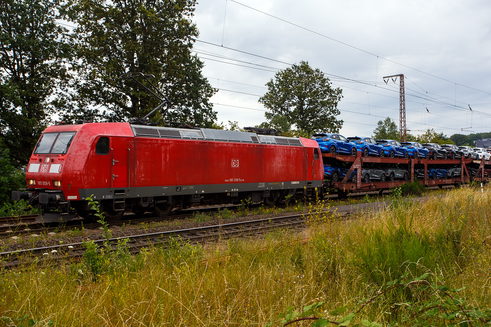 Die 185 058-5 (91 80 6185 058-5 D-DB) der DB Cargo AG fährt am 11 Juli 2024 mit einem langen beladen Autotransportzug (Wagen der Gattung Laaeks 553 der DB Cargo Logistics GmbH, ex ATG), durch Wilnsdorf-Rudersdorf (Kreis Siegen) in Richtung Siegen bzw. Kreuztal.

Nochmals einen lieben Gruß an den netten grüßenden Lokführer zurück, mich freuen immer die Grüße.

Die TRAXX F140 AC1 wurde 2002 von Bombardier in Kassel unter der Fabriknummer 33467 gebaut.