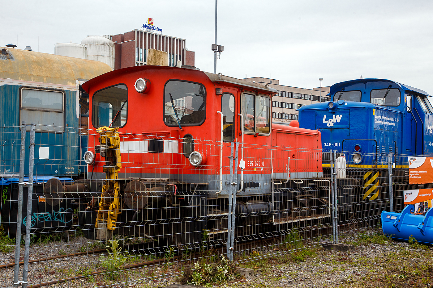 Die 335 079-0 alias 335-004 der L&W - Laeger & W�stenh�fer GmbH & Co KG Eisenbahnverkehrsunternehmen (�ber die Beteiligungsfirma Behefa GmbH & Co. KG, Berlin), ex DB 98 80 3335 079-0 D-DB, steht am 31 Mai 2022 hinter dem Zaun der iaf 2022 in M�nster.

Die K�f III mit Gelenkwelle und Funk wurde 1969 
Arnold Jung Lokomotivfabrik in Jungenthal bei Kirchen an der Sieg unter der Fabriknummer 14088 gebaut und als 333 079-2 an die DB - Deutsche Bundesbahn geliefert. 1989 erfolgte der Umbau/die Ausr�stung mit Funkfernsteuerung und somit die Umzeichnung in DB 335 079-0, im Jahr 2017 erfolgte (als 98 80 3335 079-0 D-DB) die Ausmusterung bei der DB AG und der Verkauf an die RNE Rhein-Neckar-Eisenbahnservicegesellschaft mbH in Mannheim, bereits 2018 ging sie dann an die Behefa GmbH & Co. KG in Berlin f�r die L&W (Berlin).

Die K�f III (Kleinlok mit �l-(Diesel-)Motor und Fl�ssigkeitsgetriebe, Leistungsgruppe III) hat einen MWM-Motor  (Motorenwerke Mannheim) vom Typ RHS 518A mit einer Dauerleistung von 177 kW (240 PS) bei 1.600 U/min, dessen Leistung �ber ein hydraulische Wendegetriebe L213U von Voith, von diesem �ber Gelenkwellen auf die zus�tzlich vorhandenen Achsgetriebe (nicht wie �ltere Ausf�hrung der BR 331 �ber Rollenketten) auf die Achsen geht. Die Kraft�bertragung �ber Gelenkwelle ist eine Weiterentwicklung von Gmeinder aus dem Jahre 1965. Die K�f III haben eine H�chstgeschwindigkeit von 45 km/h. 

Der Unterschied zwischen der BR 333 und 335 besteht darin, dass die BR 335 auf Funkfernsteuerung umgebaute K�f III der BR 333 sind.

TECHNISCHE DATEN:
Spurweite: 1.435 mm
Achsformel : B 
L�nge �ber Puffer: 7.830 mm 
Dienstmasse (2/3 Vorr�te): 22 t 
Dieselkraftstoff: 300 l 
H�chstgeschwindigkeit: 45 km/h 
Anfahrzugkraft: 83,4 kN
