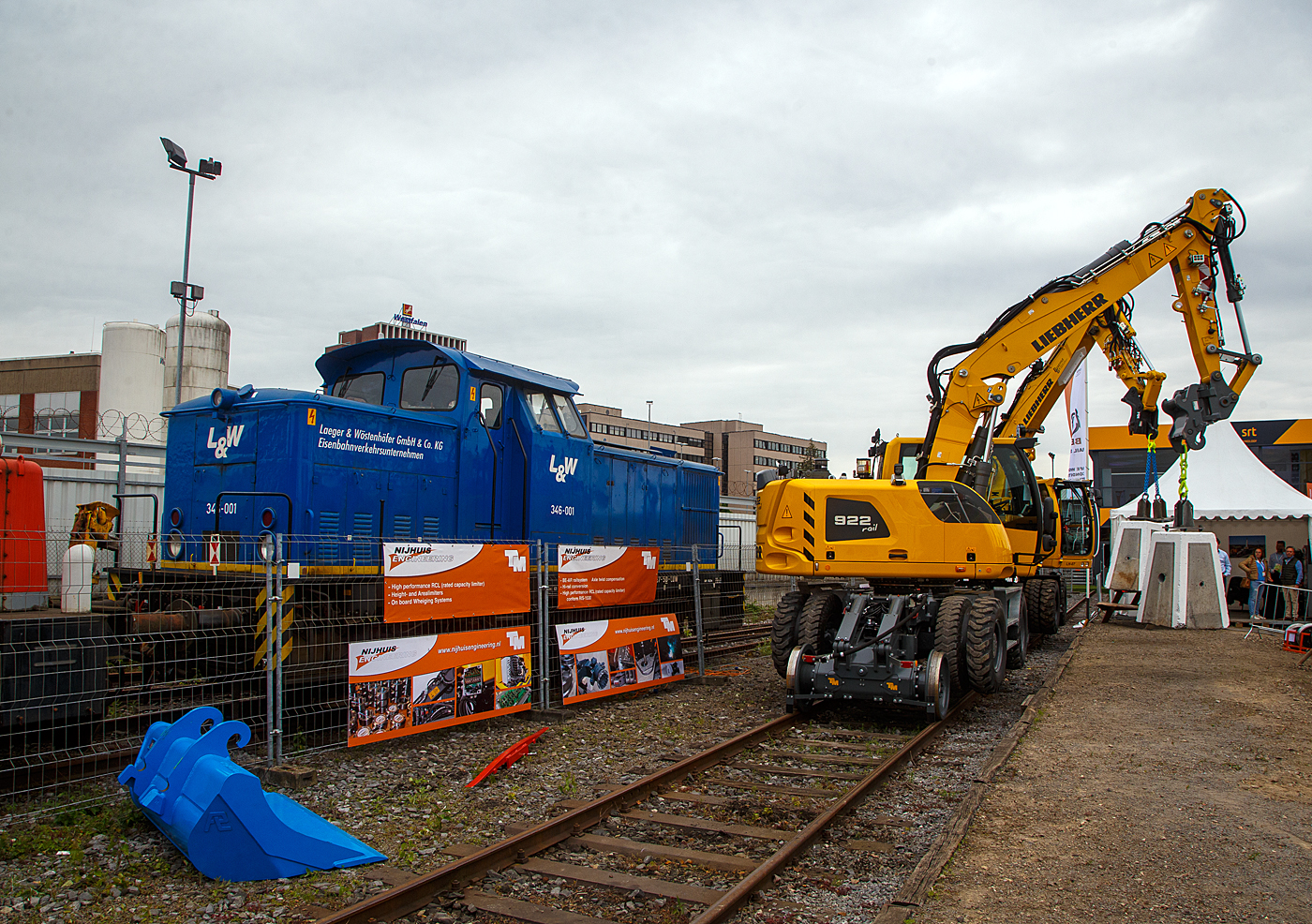 Die 346-001alias 345 387-5 (98 80 3345 387-5 D-LUW) der L&W - Laeger & Wöstenhöfer GmbH & Co KG Eisenbahnverkehrsunternehmen, ex MWB V 641 (Mittelweserbahn GmbH, Bruchhausen-Vilsen), ex Škoda Plzeň, Werk Ejpovice (CSSR, später CZ), steht am 31 Mai 2022 hinter dem Zaun der iaf 2022 in Münster.

Die V 60 ost (bzw. V 60 D oder V 60.12) wurde 1982 bei LEW (VEB Lokomotivbau Elektrotechnische Werke „Hans Beimler“, Hennigsdorf) unter der Fabriknummer 18002 gebaut und im November 1982 in die damalige Tschechoslowakei (ab 01.01.1993 Tschechische Republik)an Škoda Plzeň (Pilsen) mit der Bezeichnung  WL  fürs Werk Ejpovice (Eipowitz) ausgeliefert. Im März 2001 wurde sie nach Deutschland an die Mittelweserbahn GmbH in Bruchhausen-Vilsen als MWB V 641 verkauft. Bereits im Dezember 2004 ging sie dann an die L&W - Laeger & Wöstenhöfer GmbH & Co KG Eisenbahnverkehrsunternehmen mit Sitz in Berlin sie die Betreibernummer  346-001 bekam, seit 2007 hat sie die NVR-Nr, 98 80 3345 387-5 D-LUW.

Die vierachsigen dieselhydraulischen Rangierlokomotiven V 60 D für den mittelschweren Rangierdienst waren neben dem Einsatz bei der Deutschen Reichsbahn auch bei diversen Werk- und Grubenbahnen zu finden. Etwa 25 Prozent der Lokomotiven wurden exportiert, in RGW-Staaten und in das Nichtsozialistische Wirtschaftsgebiet. So erhielten unter anderem die Ägyptischen Staatsbahnen, die BDŽ und die SNTF diese Lokomotiven. Die Entwicklung stammt aber nicht LEW in Hennigsdorf, sondern sie wurden ab 1955 vom VEB Lokomotivbau Karl Marx Babelsberg (LKM) entwickelt die auch die ersten 188 Stück als V 60.10 bis 1964 baute. 

Rechts sind zwei LIEBHERR 922 rail Zweiwegebagger bei einer Vorführung auf der Iaf 2022, der erste Baggerführer machte mir Platz fürs freie Schußfeld, danke.
