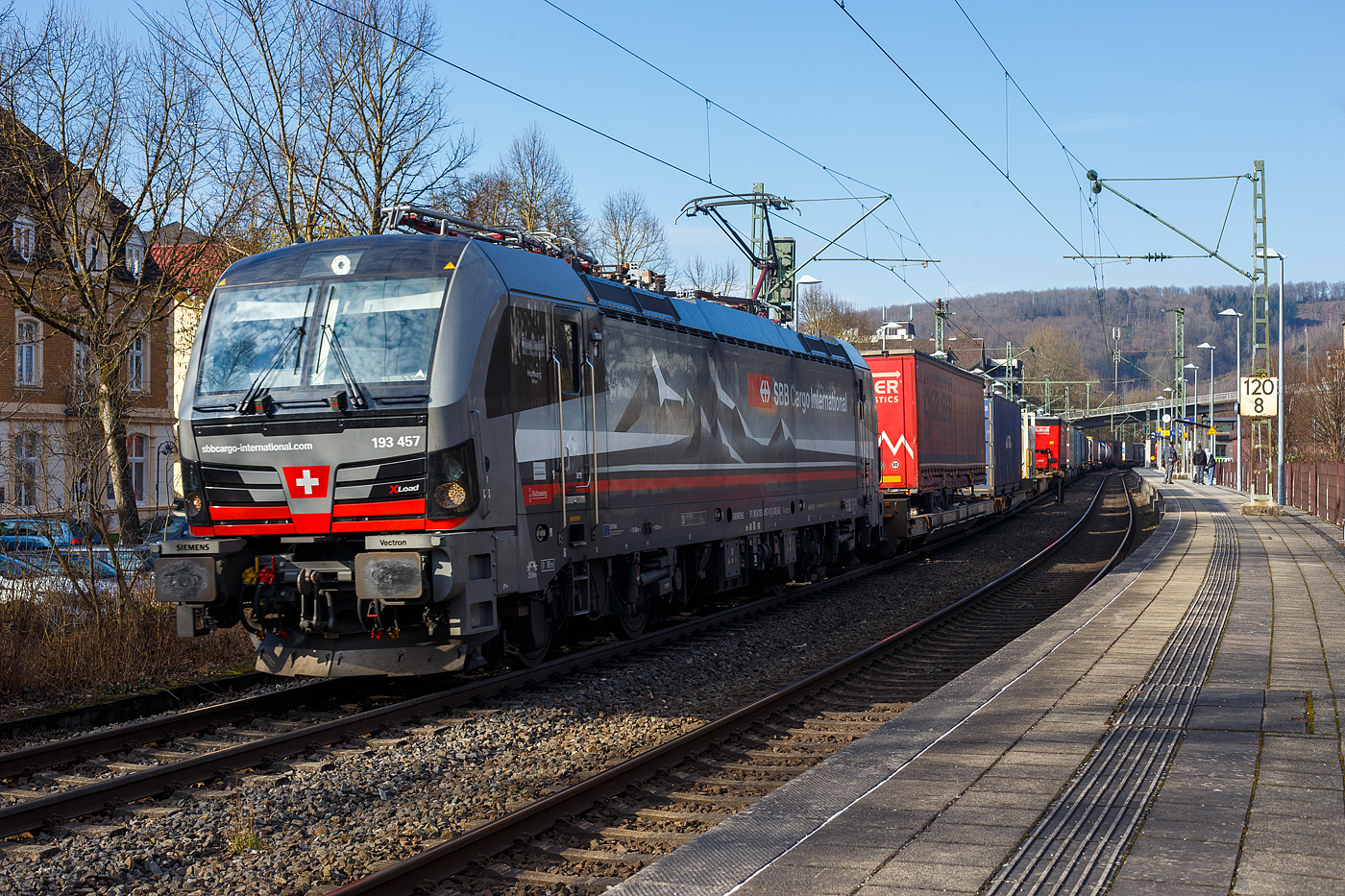 Die an die SBB Cargo International AG vermietete mit „XLoad“ ausgestattete 193 457  Hofburg Wien  (91 80 6193 457-9 D-SIEAG) der SüdLeasing GmbH, Stuttgart (eingestellt in Deutschland durch Siemens) fährt am 08 Februar 2025 mit einem KLV-Zug, durch Kirchen (Sieg) in Richtung Köln.

Die Multisystemlokomotive Siemens Vectron MS wurde 2024 von Siemens Mobilitiy in München-Allach unter der Fabriknummer 23785 gebaut und am 12.09.2024 ausgeliefert. Sie wurde in der Variante A40-1a ausgeführt und hat so die Zulassung für Deutschland, Österreich, die Schweiz, Italien, die Niederlande und Belgien (D / A / CH / I / NL / B). Sie verfügt über eine Leistung von 6,4 MW (160 km/h) und ist neben den nationalen Zugsicherungssystemen mit dem Europäischen Zugsicherungssystem (ETCS BL3) ausgestattet. Zudem ist sie mit der neuen Ausrüstungspaket XLoad ausgestattet. 

Das neue XLoad Ausrüstungspaket für Vectron:
XLoad ist ein Ausrüstungspaket für Vectron, welches künftig mitbestellt, aber auch bei bereits ausgelieferten Vectron Loks nachgerüstet werden kann. Das Feature verbessert die Reibwertausnutzung und ermöglicht dadurch höhere Anhängelasten. Zudem reduzieren die Fahreigenschaften, die das Feature bewirken, den Verschleiß von Rad und Schiene.

Aktuell sind die Schweizer Vectron-Lokomotiven (SBB Cargo und BLS Cargo) in der Regel in Doppeltraktion unterwegs. Die Steigungen und Rampen der Schweizer Berge sind vor allem bei schlechten Witterungsbedingungen nicht ohne. Eine Lokomotive muss auch bei geringerem Schlupf genügend Traktion auf die Schienen bringen, um alle Güter sicher und zuverlässig ans Ziel zu bringen. Ein effizienter Weg aus dieser «Misere» ist die für Vectron entwickelte Zusatz-Funktion «XLoad». Den erfolgreichen Beweis trat eine SIEMENS Testlokomotive im Frühjahr 2022 bei der SBB Cargo International und bei der BLS Cargo eindrücklich an. 

Für SBB Cargo International bewies die Test-Lokomotive am Bözberg und für BLS Cargo an der Nordrampe des Lötschbergs ihre enorme Zugkraft. 
Vectron meisterte im Frühjahr 2022 die lange 12‰-Steigung des Bözbergs mit einer Anhängerlast von 2.000 Tonnen bravourös. Bei den nächtlichen Testfahrten zeigte sich eindrücklich die enorme Zugkraft der Lokomotive. 

Am Lötschberg wurden bei der BLS Cargo steigungsmäßig noch ein paar Promille draufgepackt. Mit 1.020 Tonnen im Gepäck bewältigte die Vectron-Lokomotive mit XLoad-Feature die 27‰-Steigung der Nordrampe ebenfalls meisterlich. Und auch diverse Anfahrtsversuche absolvierte der mit dem XLoad-Feature aufgerüstete Vectron problemlos. 

So bestellte die SüdLeasing GmbH (Stuttgart) im Auftrag der SBB Cargo International jüngst 20 Vectron Lokomotiven mit XLoad bei SIEMENS.
