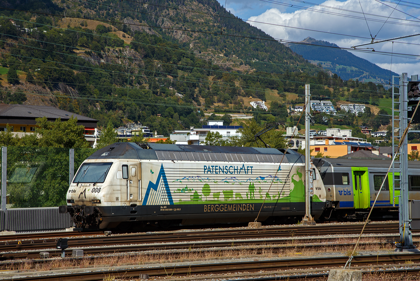 Die BLS Werbelok Re 465 008-1  Allegra , ex  Niederhorn , (91 85 4465 008-1 CH-BLS) mit Werbung Patenschaft für Berggemeinden steht am 07 September 2021 mit einem aus Einheitswagen III (EW III) bestehenden Zug in Birg.

Die Lok wurde 1994 von der SLM (Schweizerische Lokomotiv- und Maschinenfabrik) in Winterthur unter der Fabriknummer 5645 gebaut, der elektrische Teil ist von der ABB (Asea Brown Boveri).

Die Re 465 ist eine von der BLS Lötschbergbahn beschaffte elektrische, vierachsige Universallokomotive mit Umrichtertechnik. Sie ist eine Weiterentwicklung der Re 460 der SBB und gehört zur Lok-2000-Familie. Nach der Erstbestellung der BLS über acht Maschinen die 1994 gebaut wurden, folgten weitere 1997 zehn Loks (009–018) für den Huckepackkorridor. Diese Loks aus den 90er-Jahren sind für den Personen- wie für den Güterverkehr im Einsatz. Künftig werden sie auch beim Autoverlad und im Berner Oberland eingesetzt, nicht mehr im originalen Dunkelblau, sondern im leuchtenden BLS-Grün.

Zwischen 2019 und 2022 durchliefen alle 18 Loks des Typs Re465 ein Modernisierungsprogramm (Refit). Mit diesem Refit verlängert sich die Lebensdauer der rund 25-jährigen Loks um weitere 15 Jahre. Sie sind neu bis ins Jahr 2040 einsetzbar. Die modernisierten Lokomotiven sind gut zu erkennen, sie sind neu grün lackiert (diese noch nicht) und werden damit zur auffälligen und klar ersichtlichen BLS-Markenbotschafterin. Das Modernisierungsprogramm kostete insgesamt rund CHF 20 Millionen. Modernisiert wurden alle Loks in der BLS-Werkstätte Bönigen.

Im Personenverkehr zieht bzw. stößt die Re465 die GoldenPass-Express-Züge zwischen Interlaken Ost und Zweisimmen, im Güterverkehr wird sie in Mehrfachtraktion mit anderen Loks (TRAXX und Vectron) eingesetzt. Die Loks werden ab Ende 2023 auch beim Autoverlad eingesetzt und ersetzen damit die braunen Loks des Typs Re 425. Damit kann die BLS auf eine Neubeschaffung verzichten.

TECHNISCHE DATEN:
Spurweite:  1.435 mm (Normalspur)
Achsformel:  Bo’Bo’
Länge über Puffer:  18.500 mm
Drehzapfenabstand: 11.000 mm
Achsstand im Drehgestell: 2.800 mm
Höhe:  4.540 mm
Breite:  3.000 mm
Dienstmasse:  84 t
Höchstgeschwindigkeit:  230 km/h
Stundenleistung:  7.000 kW
Dauerleistung:  6.400 kW
Anfahrzugkraft:  300 kN
Treibraddurchmesser:  1.100 mm
Stromsystem:  Wechselstrom 15 kV 16,7 Hz
