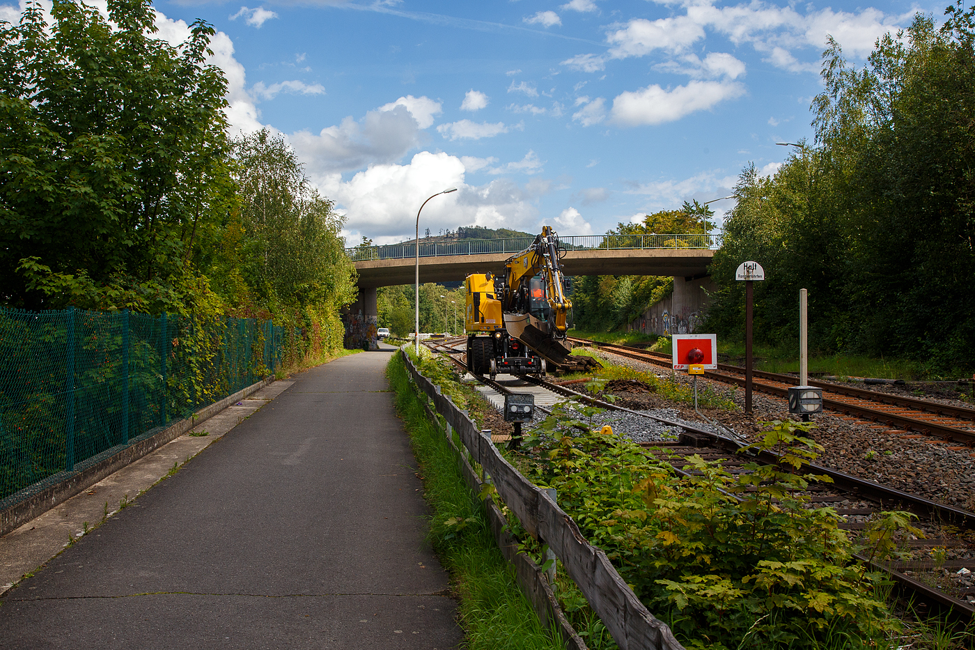 Die KSW (Kreisbahn Siegen-Wittgenstein) erneuert die ersten Gleismeter vom Anschlussgleis, zum Rangierbahnhof in Herdorf der Betriebsstätte FGE -Freien Grunder Eisenbahn (KSW NE447 / DB-Nr. 9275).

Hier am 16.08.2023 im Einsatz der Caterpillar CAT M323F Zweiwegebagger mit hydrostatischem Schienenradantrieb (Serien-Nr. RH600 189), Kleinwagen Nr. D-ZBM 99 80 9902 521-0 der ZEPPELIN Baumaschinen GmbH (Garching), ein Mietbagger vermietet an die Firma  W. Hundhausen Bauunternehmung GmbH (Siegen). Es werden die ersten Gleismeter vom Anschlussgleis erneuert, der Bagger ist bei der Einschotterung.
