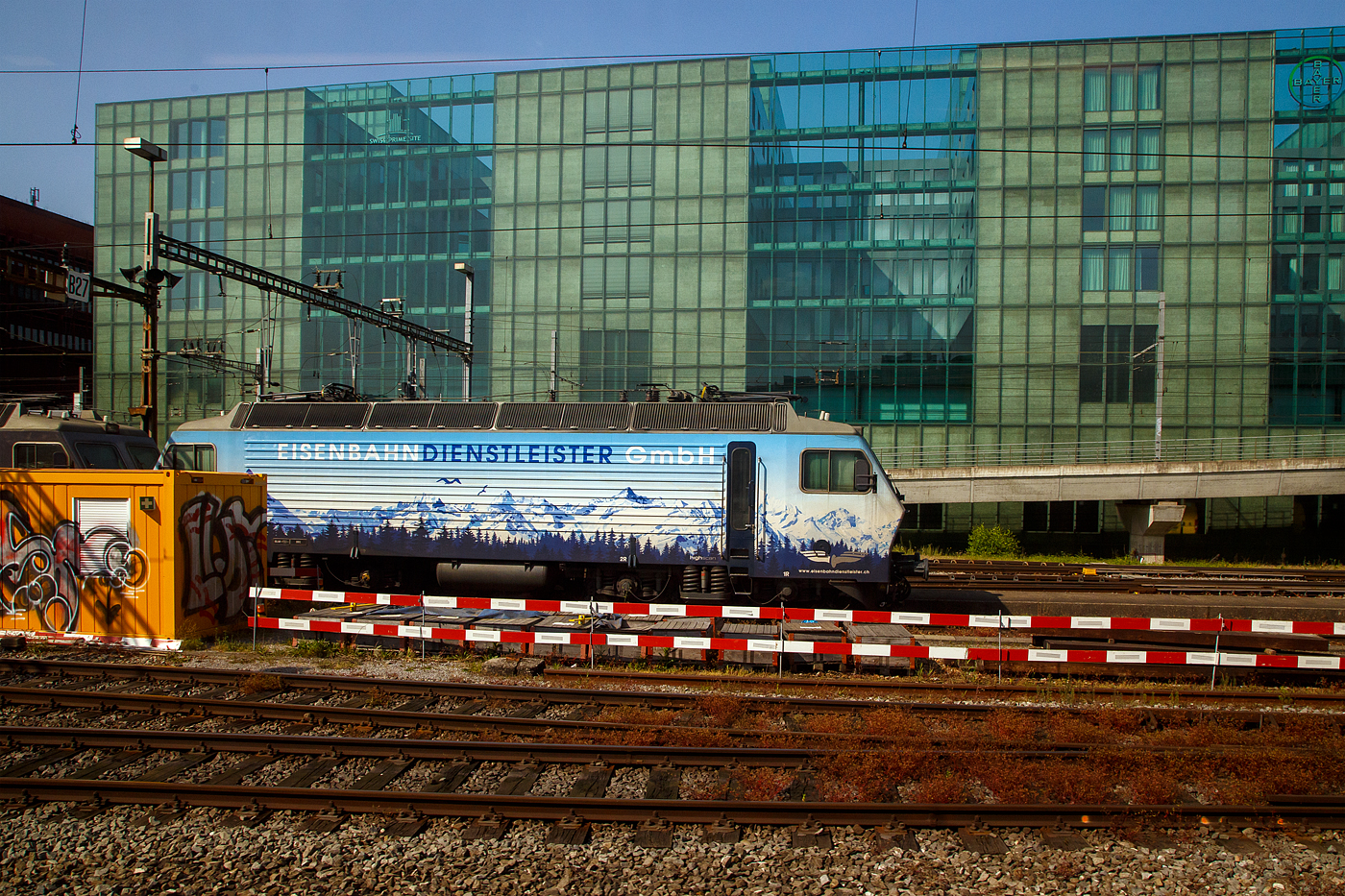 Die Re 446 018-4 (ex SOB Re 446 448, ex SBB Re 4/4 IV 10104) und dahinter verdeckt die Re 446 017-6 (ex SOB Re 446 447, ex SBB Re 4/4 IV 10103) der EDG - Eisenbahndienstleister GmbH (Thayngen) sind am 28 Mai 2023 beim Bahnhof Basel SBB abgestellt, Aufnahme aus einem ICE heraus.

Die 4 Lok der Schweizer Baureihe Re 446 wurden als vierachsige Prototyp-Lokomotiven (Projekt Bahn 2000) als Re 4/4 IV im Jahr 1982 von der SLM - Schweizerische Lokomotiv- und Maschinenfabrik in Winterthur (mechanischer Teil) und der BBC - Brown, Boveri & Cie. in Baden (elektrischer Teil) für die SBB gebaut. Aufgrund ihres lauten Luftgeräusches erhielten sie den Beinamen „Staubsauger“, alternativ wurden sie wegen der eckigen Kastenform auch „Container“ genannt. Heute sind diese vier Lokomotiven als Re 446 bei der Eisenbahndienstleister GmbH im Einsatz. 

In den 1970er-Jahren evaluierten die SBB für die Schweiz geeignete Formen des Hochgeschwindigkeitsverkehrs. Das Projekt Bahn 2000 nahm allmählich Form an und verschiedene Kosten-Nutzen-Analysen führten zur Erkenntnis, dass Infrastruktur und Rollmaterial für eine Geschwindigkeit von maximal 200 km/h ausgelegt werden sollten. Die im Einsatz stehenden und zuverlässigen Re 4/4II waren für diesen Zweck zu schwer. Die eingesetzte Technik kann nicht mehr Leistung liefern. Richtungsweisend war der Einsatz der Gleichrichtertechnik, welche allerdings noch in den Kinderschuhen steckte und bei den seit 1974 im Einsatz stehenden Prototyp-Triebzügen RABDe 8/16 ständige Probleme bereitete.

Aufgrund dieser bekannten Fehleranfälligkeit stellten die SLM und die BBC gemeinsam vier Prototyp-Lokomotiven her, welche in den Grundzügen den RABDe 8/16 gleichen. Um Gewicht einzusparen wurden die Lokomotiven in Leichtstahl-Bauweise ausgeführt, um die schwere Technik unterbringen zu können, dadurch kann die Achslast bei 20 Tonnen gehalten werden. Analog zu den RABDe 8/16 kamen von Gleichrichtern gespeiste Wellenstrommotoren zum Einsatz. Da es sich um Prototypen handelt, bekamen zwei Lokomotiven Getriebe von BBC, die anderen beiden solche von der SLM. Die eingesetzte Technik erlaubte eine Höchstgeschwindigkeit von 160 km/h und die Dauerleistung von etwas über 5.050 kW bei etwa 85 km/h.

Anfang 1983 erbrachte die 10104 im Heitersberg-Tunnel den Nachweis, dass sie die Geschwindigkeit von 175 km/h erreichen kann, welche notwendig ist, um eine Zulassung für 160 km/h zu erhalten. 

Die Lokomotiven verfügen über eine elektrische Bremse, die aber nur als Widerstandsbremse ausgeführt ist, da der Stand der Technik 1982 die Rekuperationsbremsung mit Thyristorsteuerung noch nicht erlaubte. Es zeigte sich auch, dass die Entstörungsmassnahmen aufwändiger waren als zunächst erwartet.

Trotz ständiger Verbesserungen an der Lok-Technik und ausgebügelter Kinderkrankheiten stand 1985 fest, dass die Lokomotive nicht in Serie gehen würde. Die für 1990 geplante Einführung der S-Bahn Zürich stand für die SBB im Vordergrund, während ein kurzzeitiger Verkehrsrückgang und die sich verzögernden Neubaustrecken erst mittelfristig entsprechendes Rollmaterial benötigten. Studien von SLM und BBC belegen darüber hinaus, dass die gewünschte universelle Hochgeschwindigkeitslokomotive für 200 km/h, die heute als SBB Re 460 existiert, noch weiterer Entwicklungsarbeit bedurfte. Die SBB gingen darauf ein und vergaben einen entsprechenden Entwicklungsauftrag. Anfänglich war eine Typenbezeichnung Re 4/4 VI vorgesehen. Die vier Re 4/4IV bleiben damit Einzelexemplare.

Einsatz und Werdegang bei den SBB
Die Lok waren insbesondere am Genfersee, im Wallis und gelegentlich auch zwischen Zürich und St. Margrethen anzutreffen. Im Jahr 1984 lautete ein Werbeslogan der SBB «In Zukunft die Bahn». Auf verschiedenen Bahnhöfen wurde eine Leistungsschau mit verschiedenem Rollmaterial durchgeführt. Ende 1986 bekamen alle vier Maschinen, die dem Depot Lausanne zugeteilt waren, eine einheitliche Lackierung im sogenannten verkehrsrot und der bis 1992 prägenden Bahn-2000-Werbung. Die großzügig ausgebaute Strecke im Rhonetal diente den SBB als Versuchsstrecke und war lange Zeit der einzige nennenswerte Abschnitt, welcher punktuell mit bis zu 160 km/h befahren werden konnte. Anfang 1987 folgten weitere Geschwindigkeitsversuche, bei welchen eine der Loks 188 km/h erreichte und ein Dreigespann den Schweizer Geschwindigkeitsrekord von 192 km/h aufstellte, welcher 1992 von den Re 460 gebrochen wurde.

Der Unterhalt der Prototypen-Serie gestaltete sich im Vergleich zu den Großserien als äußerst kostenintensiv. Deshalb versuchten die SBB die vier Maschinen zu verkaufen und auch auf die vorgesehene Umzeichnung (Re 440 000–003) ins 1992 eingeführte UIC-konforme Nummernschema zu verzichten. Mit der SOB verständigte man sich schließlich auf einen Fahrzeugtausch: die vier Re 4/4IV gingen an die SOB, die SBB übernahmen im Gegenzug vier Re 4/4III.

Im Dezember 1994 übernahm die SOB die ersten zwei Re 4/4IV von den SBB, allerdings zog sich der «Tausch» der restlichen beiden Loks noch bis 1996 hin. Bei den SOB erhielt die Kleinserie ihre neue Bezeichnung Re 446 (Re 446 445–448).

Anlässlich der Fusion der SOB mit der BT wurde 2001 ein neues Nummernschema eingeführt, weshalb die Re 446 445–448 umgezeichnet wurden und neu als Re 446 015–018 verkehren. 

Seit der Übernahme 1995 setzte die SOB die Lokomotiven vornehmlich im Voralpen-Express auf der Achse (Romanshorn –) St. Gallen – Luzern ein. Anfangs wurden diese Züge mit Wagen des Typs EW IV geführt. Ab 1999 verkehrten die Züge mit modernisierten Wagen des Typs Revvivo. Die Züge wurden nun verpendelt, wobei nur drei Steuerwagen die Vielfachsteuerung IIId erhielten und somit Re-446-tauglich waren.

Bis Dezember 2019 wurde der Voralpen-Express auf neue Garnituren des Typs Stadler Flirt «Traverso» umgestellt. Die vier Lokomotiven Re 446 wurden daraufhin an die Eisenbahndienstleister GmbH (EDG) verkauft.

TECHNISCHE DATEN:
Spurweite: 1.435 mm (Normalspur)
Achsfolge: Bo' Bo'
Länge über Puffer: 15.800 mm
Drehzapfenabstand: 7.900 mm
Achsabstand im Drehgestell: 2.900 mm
Treibraddurchmesser: 1.260 mm (neu)
Leistung: 4.960 kW
Höchstgeschwindigkeit: 160 km/h
Gewicht: 80.0 t
Anfahrzugkraft: 300 kN
Dauerzugkraft: 210 kN
Fahrleitungsspannung: 15000 V, 16.7 Hz ~
