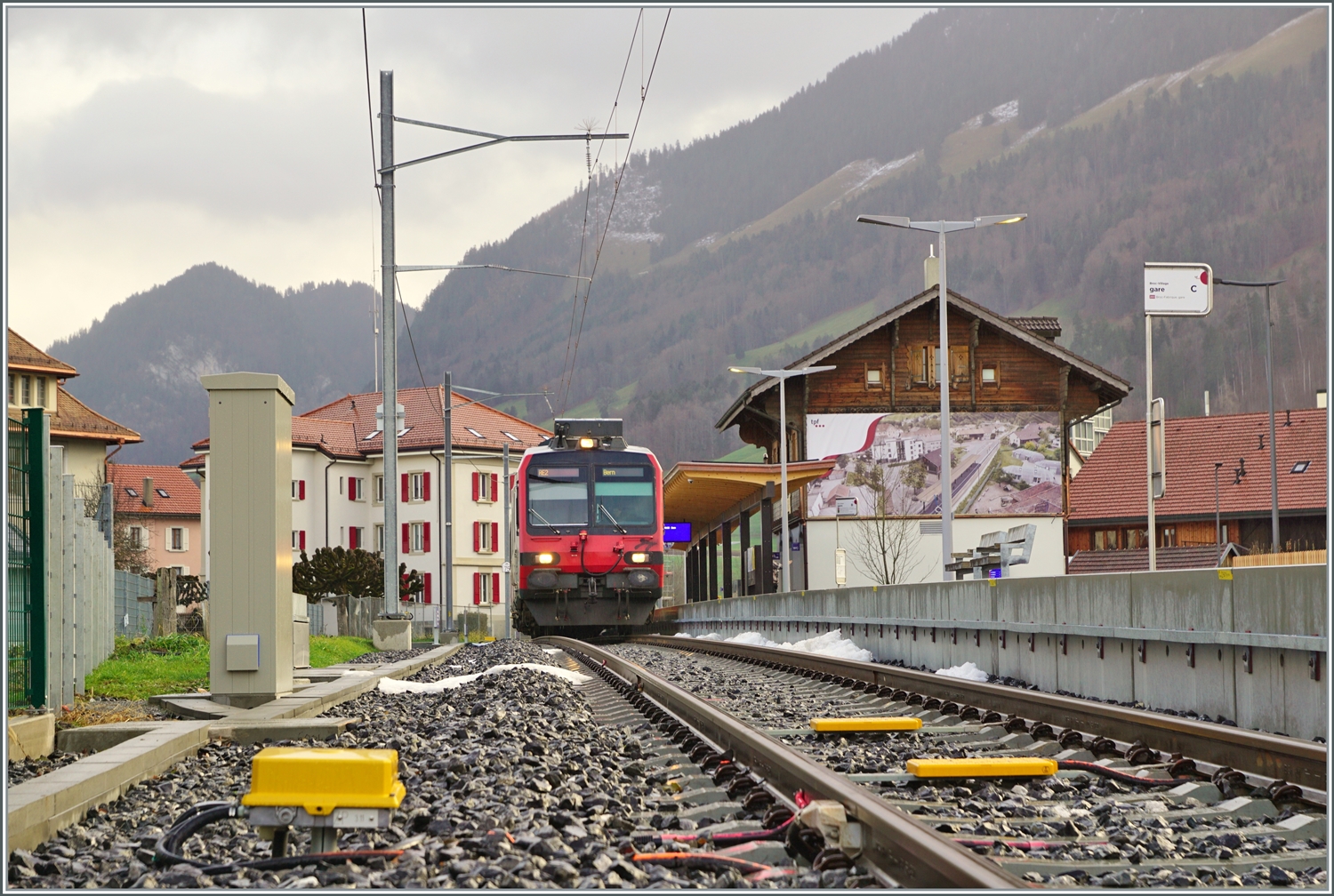 Ein Bild, welches nur eine relativ kurze Zeit gemacht werden kann: Während der SBB RBDe 560 Domino in Broc Villages wendet, kann vom geöffneten Bahnübergang der Zug und die näher Umgebung des Bahnhofs von Broc Village fotografiert werden. Wird der Zug ab August von Bulle Fabrique kommen, dürfte bei der Ankunft des Zuges die Barriere bereits geschlossen sein.

22. Dezember 2022