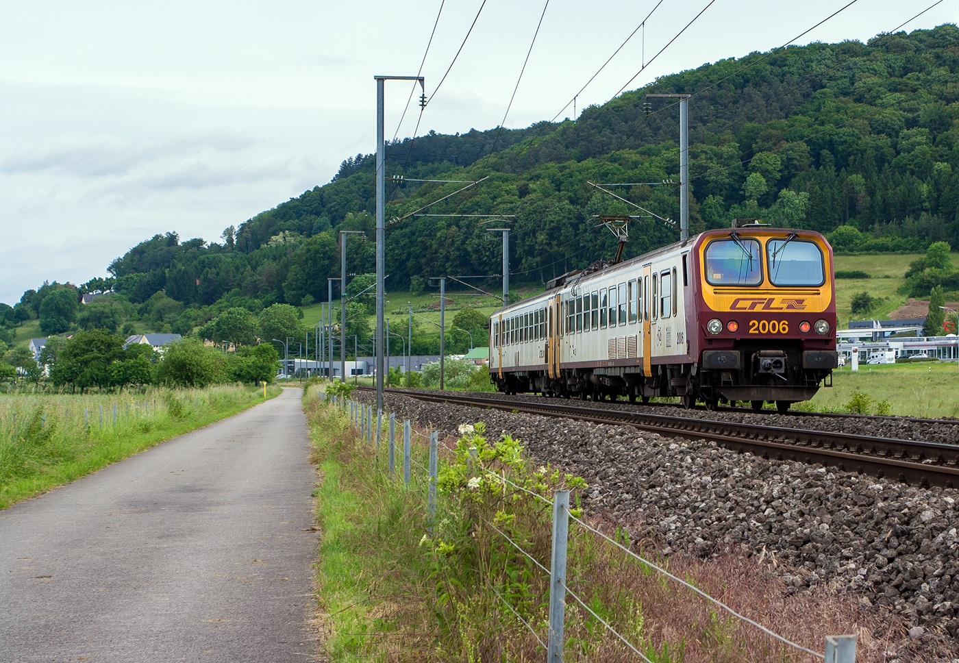 Ein CFL Z2 – CFL Série 2000, der CFL 2006 (94 82 00 2006 1-x L-CFL / 94 82 00 2006 2-x L-CFL) fährt am 15 Juni 2013 auf der Nordstrecke (Bahnstrecke Luxemburg–Spa), hier bei Lintgen in Richtung Mersch.

Das Bild ist schon „historisch“ bis Ende dieses Jahres (2025) sollen alle Z2 Luxemburg in Richtung Rumänien verlassen haben. Sie wurden von dem Unternehmen Ferotrans TFI (ein neuer Akteur auf dem rumänischen Markt) übernommen. So dürfen sie wohl nach 35 Jahren in Luxemburg im Einsatz noch weitere Jahre in Rumänien fahren. 

Die CFL-Serie 2000 ist eine Serie von 22 elektrischen Triebwagen (Doppeltriebwagen bestehend aus Triebfahrwagen und Beiwagen), die von der CFL (Société Nationale des Chemins de Fer Luxembourgeois, deutsch Nationale Gesellschaft der Luxemburgischen Eisenbahnen) zwischen 1990 und 1992 mit den Nummern 2001-2022 in Betrieb genommen wurden. Diese Fahrzeuge sind unter den Eisenbahnern auch als „Z2“ bekannt.

Die Z2 basieren auf der Familie zweiteiliger elektrischer Triebwagen der französischen Staatsbahn SNCF der 1980er Jahren (Z 7300, 7500 für 1500 V =, Z 11500 für 25 kV 50Hz AC und 9500, 9600 für Zweisystem). Die luxemburgische Eisenbahn (CFL) beschaffte 22 dieser Triebwagen (25 kV 50Hz AC) für Einsätze im Nahverkehr. Durch die große Höchstgeschwindigkeit von 160 km/h werden sie auch für Zugläufe auf größeren Entfernungen eingesetzt. Die Bezeichnung Z2 leitet sich vom Bezeichnungssystem für französische Schienenfahrzeuge ab, wo der Kennbuchstabe Z für elektrische Nahverkehrstriebwagen steht, dem eine 2 für zweiteilig hinzugefügt wurde.

Entstehung:
Gegen Ende der 1970er Jahre wollte die SNCF neue elektrische Triebwagen anschaffen, um einerseits ältere elektrische Fahrzeuge abzulösen, die teilweise noch aus den 1920er Jahren stammten und andererseits, um auf neu elektrifizierten Strecken die bisherigen Dieselfahrzeuge zu ersetzen. Man entschied sich für einen schnellen, zweiteiligen Triebwagenzug in Stahl-Leichtbauweise, der den gestiegenen Komfortansprüchen Rechnung tragen sollte. Die Beschaffung geschah über das Konsortium Francorail, einem Zusammenschluss der größeren französischen Eisenbahnlieferanten Alsthom, ANF, De Dietrich, Carel et Fouché, Jeumont-Schneider, MTE und TCO. Zwischen 1980 und 1988 wurden 168 Züge in fünf verschiedenen Varianten gebaut und an die SNCF geliefert. Nach der Bestellung der CFL wurden dann zwischen 1990 und 1992 weitere 22 Fahrzeuge für die CFL, mit dem Stromsystem 25 kV, 50 Hz ~, gebaut und geliefert. 

Das Fahrzeug:
Aufbau:
Ein Triebzug besteht aus zwei Teilen: einem vierachsigen, auf allen Achsen angetriebenen Triebwagen und einem antriebslosen Steuerwagen mit jeweils einem Führerstand. An den Wagenenden ohne Führerstand sind beide Wagen miteinander gekuppelt und durch einen Personenübergang verbunden. Triebwagen und Steuerwagen besitzen pro Längsseite je 2 einflügelige Schwenkschiebetüren der Bauart der französischen Einheitswagen vom Typ VSE, der Zugang ist von außen über drei Stufen möglich. Als Laufdrehgestelle fanden der Bauart Y 32 Verwendung. An den Führerstandsenden befinden sich normale, sehr breit ausgeführte Puffer als Stoßvorrichtungen und dazwischen automatische Scharfenbergkupplungen mit oberhalb liegendem Kontaktaufsatz und in das Kupplungsprofil integrierten Luftkupplungen.

Innenraum:
Die Führerstände besitzen keine Außentüren, der Zugang erfolgt ausschließlich durch die vorderen Fahrgasträume. Zwischen den Großräumen und den Einstiegsräumen und als Trennung zwischen erster und zweiter Klasse sind gläserne, pneumatisch per Handhebel betätigte Schiebetüren eingebaut. Im Gegensatz zu den früher gebauten Nahverkehrstriebwagen, die noch mit Sitzen in 2+3-Anordnung ausgestattet waren, wurden die Sitze der Z2 erstmals in einer 2+2-Anordnung in Großräumen mit Mittelgang eingebaut. In den Zügen der CFL waren auch die Sitze der zweiten Klasse bereits ab Werk stoffgepolstert. Die erste Klasse befindet sich im Triebwagen, der Steuerwagen ist komplett der zweiten Klasse vorbehalten. Die Fenster einer Wagenseite in den Fahrgasträumen lassen sich per Kurbelantrieb um etwa 20 cm öffnen, eine innen schräg angebrachte Scheibe leitet den Fahrtwind ab und verhindert ein Hinauslehnen. Die Fenster der gegenüber liegenden Fahrzeugseite sind feststehend und lassen sich nicht öffnen. Oberhalb der Fenster sind längs der Wagenseiten Gepäckablagen aus Metall angebracht. Die Triebwagen der SNCF besitzen einen Gepäckraum; die CFL verzichtete auf diesen. Im Steuerwagen ist beim Einstiegsraum am Kurzkupplungsende eine Toilettenkabine eingebaut.

Elektrische Ausrüstung:
Alle Z2-Varianten werden von vier eigenbelüfteten Gleichstrommotoren vom Typ TAB 676 B1 auf allen Achsen des Triebwagens angetrieben. Dabei sind die zwei Motoren eines Drehgestells dauerhaft in Reihe geschaltet. Aus Kostengründen entschied man sich dafür, die elektrische Ausrüstung ähnlich zu der in den Triebwagen der Reihe Z 5300 bewährten auszuführen. Die Fahrzeuge der SNCF für das Gleichstromnetz und die Zweisystemfahrzeuge werden deshalb über herkömmliche Anfahr- und Bremswiderstände gesteuert, die in den langen Dachaufbauten auf dem Triebwagen untergebracht sind. Erst die Einsystem-Wechselstromfahrzeuge erhielten eine moderne Thyristorsteuerung und daher deutlich kleinere Dachaufbauten. Der Einholmstromabnehmer für das Gleichstromnetz der SNCF mit 1.950 mm breiter Palette und vier Schleifleisten ist auf dem Triebwagen angebracht, der für das Wechselstromnetz mit schmalerer, 1.450 mm breiter Palette und zwei Schleifleisten befindet sich auf dem Steuerwagen. Mehrsystemfahrzeuge sind mit beiden Stromabnehmern ausgerüstet. Die Steuerung erlaubt die Mehrfachtraktion von bis zu drei Einheiten.

CFL Série 2000 (Typ Nahverkehr) für 25 kV Wechselspannung mit 50 Hz:
Ab Mitte der 1980er Jahre bis zur Jahrtausendwende wurden alle im Personenverkehr bedienten Eisenbahnstrecken in Luxemburg elektrifiziert, Taktverkehr und günstige Fahrpreise wurden eingeführt. Für diese ausgeweiteten Leistungen benötigten die CFL moderne elektrische Triebfahrzeuge. Man griff auf den aus Frankreich bereits bekannten Typ Z 11500 zurück, der ohne wesentliche Änderungen in 22 Exemplaren für die CFL bestellt wurde. Lediglich auf den Einbau eines Gepäckraumes wurde in Luxemburg verzichtet. Die Züge wurden zwischen 1990 und 1992 abgeliefert. Trieb- und Steuerwagen tragen die gleiche Betriebsnummer, sie wurden als 2001 bis 2022 in den Fahrzeugpark der CFL eingereiht. Der Triebwagen des Zuges 2003 wurde im Jahr 1997 bei einem Unfall zerstört und durch einen Nachbau ersetzt, der zusammen mit dem Steuerwagen 2003 wieder unter dieser Nummer eingesetzt wurde. Im Gegensatz zur SNCF kuppelten die CFL bei langwierigen Wartungsarbeiten an Einzelwagen gelegentlich Einheiten aus Trieb- und Steuerwagen unterschiedlicher Garnituren zusammen. Solche Zusammenstellungen wurden bei Verfügbarkeit beider Wagen einer Einheit wieder aufgelöst. Eine Einheit wurde mittlerweile verschrottet. 

2025 wurden mit einer Ausnahme alle (20) Fahrzeuge nach Rumänien verkauft, bleiben aber noch teilweise im Dienst der CFL bis die neuen Einheiten der CFL-Baureihe 2400 die Alstom Coradia Max-Triebwagenserie ausgeliefert waren, welche nun die Strecken des Z2 übernehmen. Lediglich das Fahrzeug 2021 verbleibt bei der CFL als Teil des Eisenbahnerbes Luxemburgs. Bis Ende 2025 sollen alle 20 Z2 Luxemburg in Richtung Rumänien verlassen haben und die letzten Triebwagen in Rumänien ankommen. Sie wurden von dem Unternehmen Ferotrans TFI (ein neuer Akteur auf dem rumänischen Markt) übernommen. So dürfen sie wohl nach 35 Jahren in Luxemburg im Einsatz noch weitere Jahre in Rumänien fahren.

In der Zentralwerkstatt der CFL erhielten die Triebwagen dafür nochmals ein Reengineering und einen letzten Feinschliff so sind die Z2 nun bereit für ein neues Leben in Rumänien.

TECHNISCHE DATEN:
Gebaute Anzahl: 22 für die CFL (SNCF 168 in unterschiedlichen Ausführungen)
Die Hersteller (unter Leitung von De Dietrich):
- mechanischer Teil: De Dietrich, Reichshoffen (Elsass)
- elektrischer Teil: GEC Alsthom, Saint-Ouen-sur-Seine (heute Alstom S.A)
- Triebdrehgestell und Laufdrehgestell: ANF - Industrie, Crespin
- Brems-, Pneumatische-Ausrüstung: Wabco-Westinghouse
- Haupttransformator: Jeumont - Schneider
- Antriebsmotoren: GEC Alsthom

Spurweite: 1.435 mm (Normalspur)
Achsformel: Bo'Bo'+2'2' (Nicht wie viele Quellen sagen 2'Bo'+2'2')
Länge über Kupplung: 50.200 mm (2 x 25.100 mm)
Fahrzeughöhe: 3.680 mm (4.300 über Stromabnehmer)
Fahrzeugbreite: 2.848 mm
Drehzapfenabstände: 17.850 mm / 6.700 mm / 18.250 mm
Achsabstand in den Antriebs-Drehgestellen: 2.600 mm
Achsabstand in den Lauf-Drehgestellen: 2.560 mm
Treibrad Durchmesser: 1.000 mm (neu)
Laufrad Durchmesser:  890 mm (neu)
Fußbodenhöhe: 1.250 mm
Eigengewicht: 108,12 t
Bremsgewicht: 145 t
Anzahl der Fahrmotoren: 4 Stück Typ TAB 676 B1, 750 V, eigenbelüftet
Leistung: 1.200 kW	 
Höchstgeschwindigkeit: 160 km/h
Stromsystem: 25 kV AC 50Hz
Sitzplätze: 168, davon 24 - 1. Klasse / 144 (davon 6 Klappsitze) - 2. Klasse
Stehplätze: 116
Kupplungstyp: Scharfenberg-Kupplung

Der Stromabnehmer befindet sich auf dem Beiwagen. 

Quelle: CFL und Wikipedia
