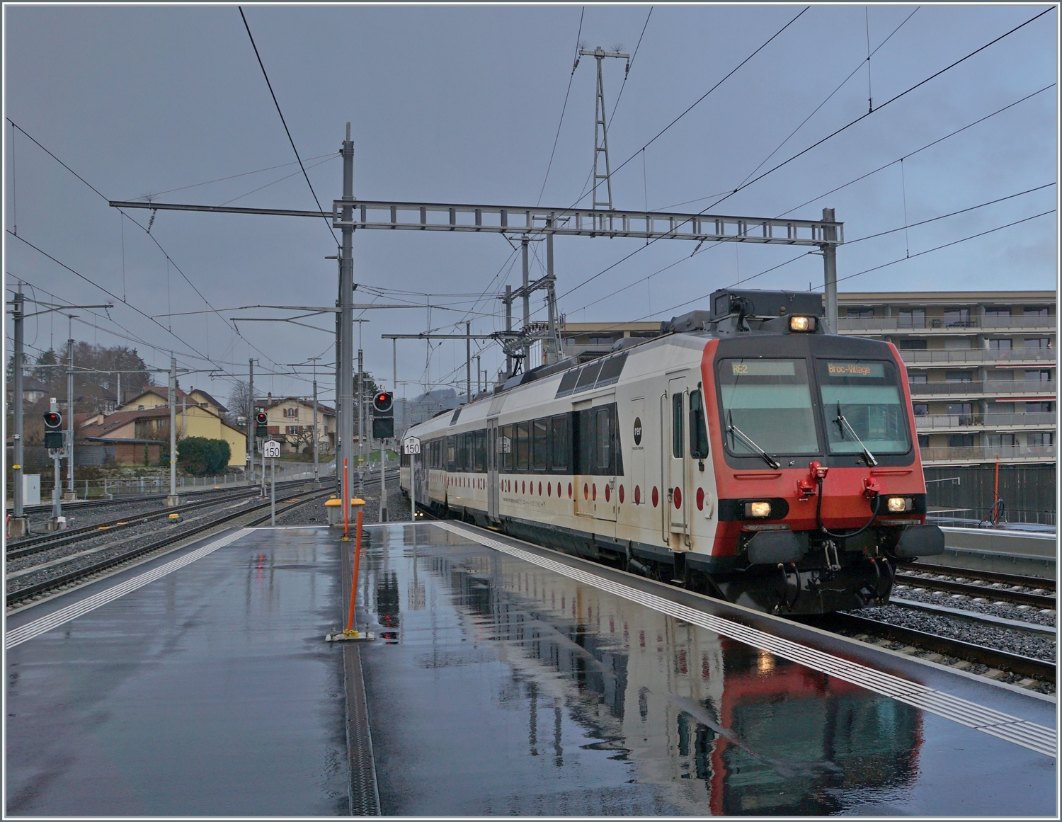 Ein TPF Regionalzug nach Broc Village (und sein Spiegelbild) erreichen Bulle. 

22. Dez. 2022